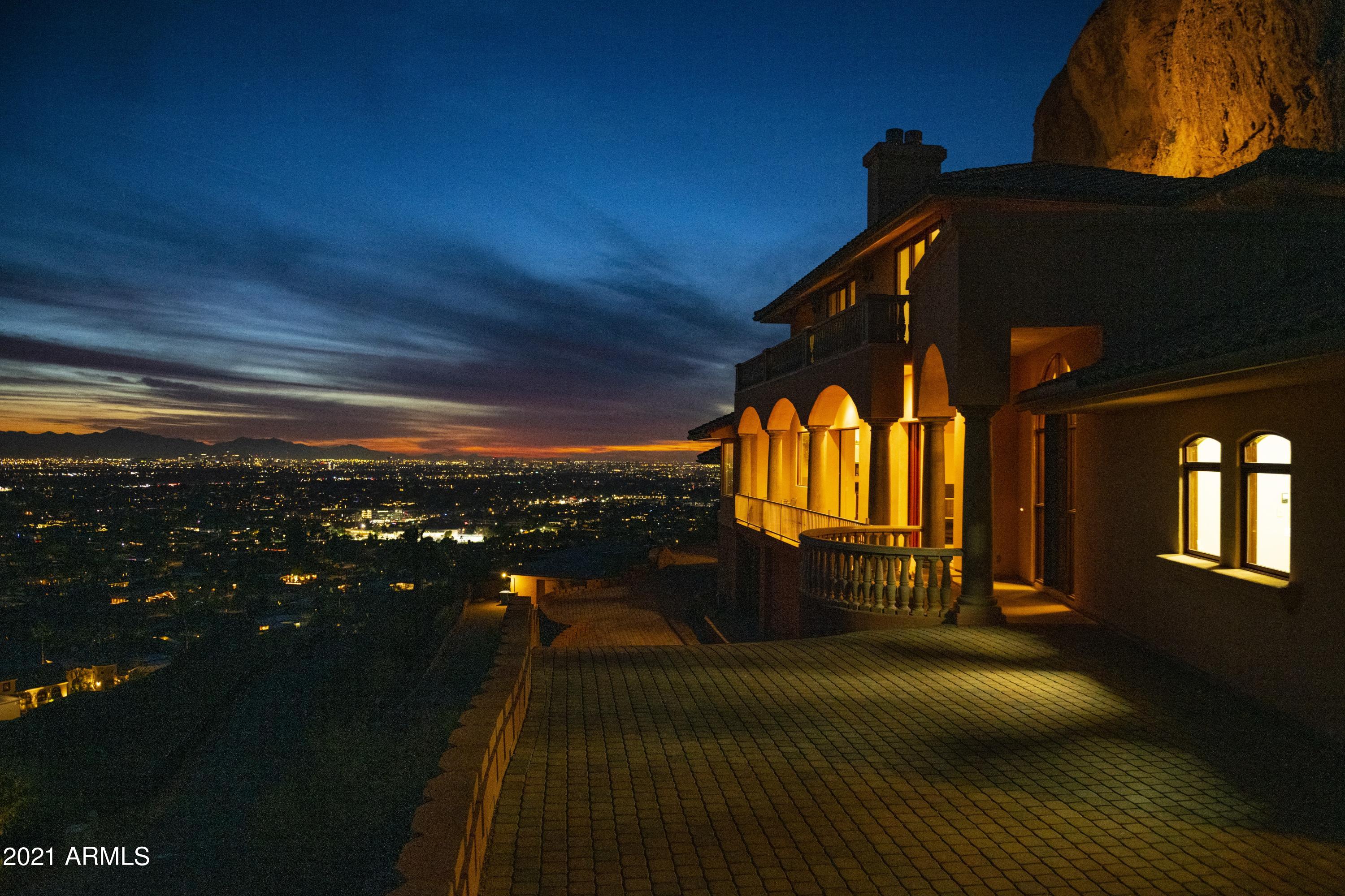 The Camel's Eye could be your backyard! Nestled on a Camelback Mountain ledge is this imposing three story walkout home offering a sweeping panoramic view of the valley and breath-taking sunsets. Amazing construction and gracious entertaining. You'll enjoy showing off your auto collection inside the 6+ stall mountain cave garage & partying with dozens of your friends in the red-rock-wine cellar. The main great room has 12' ceilings and a fully retractable window wall which leads to a paver viewing deck. Upper level owner suite has a wrap-around deck. Total of 5500 square feet, 3 bedrooms, 5 ba, multiple living areas. Room for a future infinity pool. This is the only one in the world and a rare chance to live in it, remodel it, or add to it! Some photos digitally enhanced to show options.