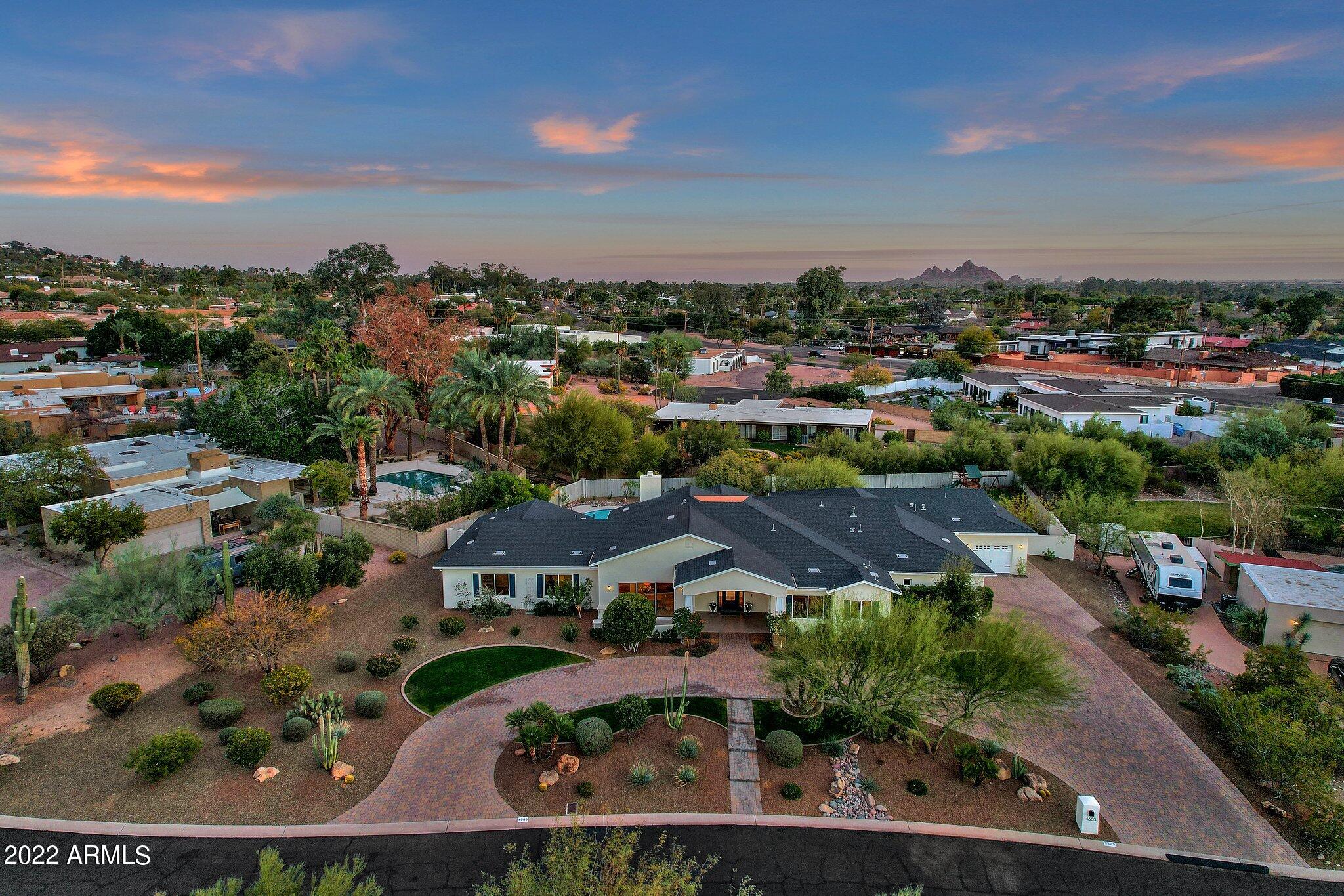Boasting a wow first-impression flattered by a long pavered semi-circular drive and a chandelier-lit portico entry, this warm and welcoming home is exquisitely sited on an oversized view-rich lot in Arcadia, one of Phoenixs most highly sought-after neighborhoods. Ideal for entertainers who appreciate an ambience of effortless elegance, the floorplan is equally perfect for child-centric families thanks to a bevy of big bedrooms, roomy baths and a cabinetry/hook-filled drop-zone designed for backpacks, books, briefcases and more. Interior highlights: Sleek/chic kitchen with snow-white cabinetry, silver-hued subway-tile backsplash, Thermador appliances, deep farmhouse sink, huge sheer-glass doors to alfresco amenities. Dining room with easy-access to Camelback-view coffee/cigar patio. Primary suite with lavish private bath, walk-in dressing closet with wealth of storage options. Rear grounds: Sparkling cool-blue pool. Lush lawn. Luxurious custom landscaping. Multiple dining, cocktail, conversation patios. Large lounge/sun-decks. Kids play area. Also: Electric-vehicle charging station. Smart-system for audio, video, lighting, security. Details: 5BD; 4BA; 4,330SF. Lot size: 2/3-acre.