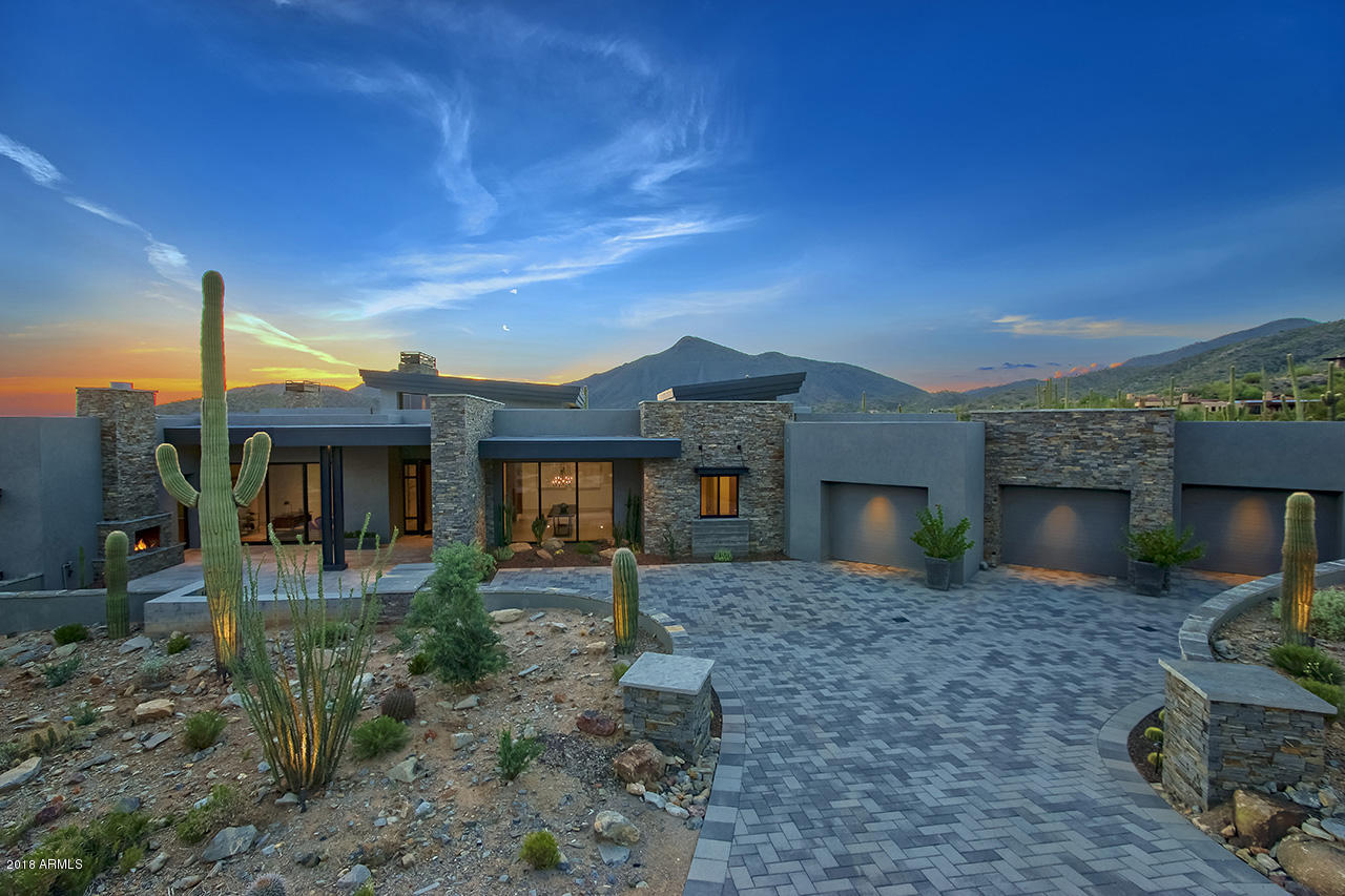 Impeccable brand new modern build located in the prestigious Saguaro Forest community of Desert Mountain. From the moment you pull up to this captivating home, you will immediately notice a perfect palette of stone, metal, glass and wood, which compliments the highest quality materials incorporated in this exclusive build. Attention to detail is key for one to truly appreciate the flow of this 6000 sq ft 4 bed 5 bath home. The inviting entry welcomes you with a courtyard fireplace, tongue and groove patio ceiling, and large iron and glass pivoting front door, which all set the tone for the state of the art modern architectural designs. Upon entering, the foyer features, walnut wood wrapped columns and a temperature controlled wine rack. Walnut shelves continuing into the dining room creating the perfect ambiance for any guest. The coffered ceiling, striking 18 foot slate tiled fireplace, and pocket sliding door in the great room, are awe inspiring.  Excellence in kitchen detail with floor to ceiling glass wall in the breakfast area, double Carrara marble waterfall islands, book matched cabinetry, and gourmet Wolf and Sub Zero appliances. The La Cornue Le Chateau 150 range is the culminating statement piece of the kitchen. Across from the walk in pantry there is also the elegance and convenience of a butlers pantry with hand rubbed black walnut cabinets and wine cooler. Spacious study / library offers floor to ceiling cabinets, half bath and courtyard access. DuChateau wood flooring, Sub Zero mini fridge, separate sitting area, and private fireplace encased with Linac marble, are exceptional features in the master suite. Bold walk-in shower and separate tub in master bathroom with his and her water closets and vanities. Abundantly sized master closet offers beautiful island and hidden stackable washer and dryer. Two additional ensuite bedrooms each having backyard access, also offer walk in closets. Many Arizona sunsets and beautiful mountain views await to be experienced from the spacious covered patio, which offers dual fireplace, bbq, and ample sized pool and spa. 1 Bed/1 Bath guest quarters with kitchenette, provides a lovely city view from it's own private patio. 4 car garage offers 240V charging station for electric vehicles and ultra quite Sommer garage door openers. In order to truly appreciate this home you will need to experience it. Too many additional upgrades and features to list. Here is your opportunity to own an unparalleled modern new build in Saguaro Forest in Desert Mountain community.