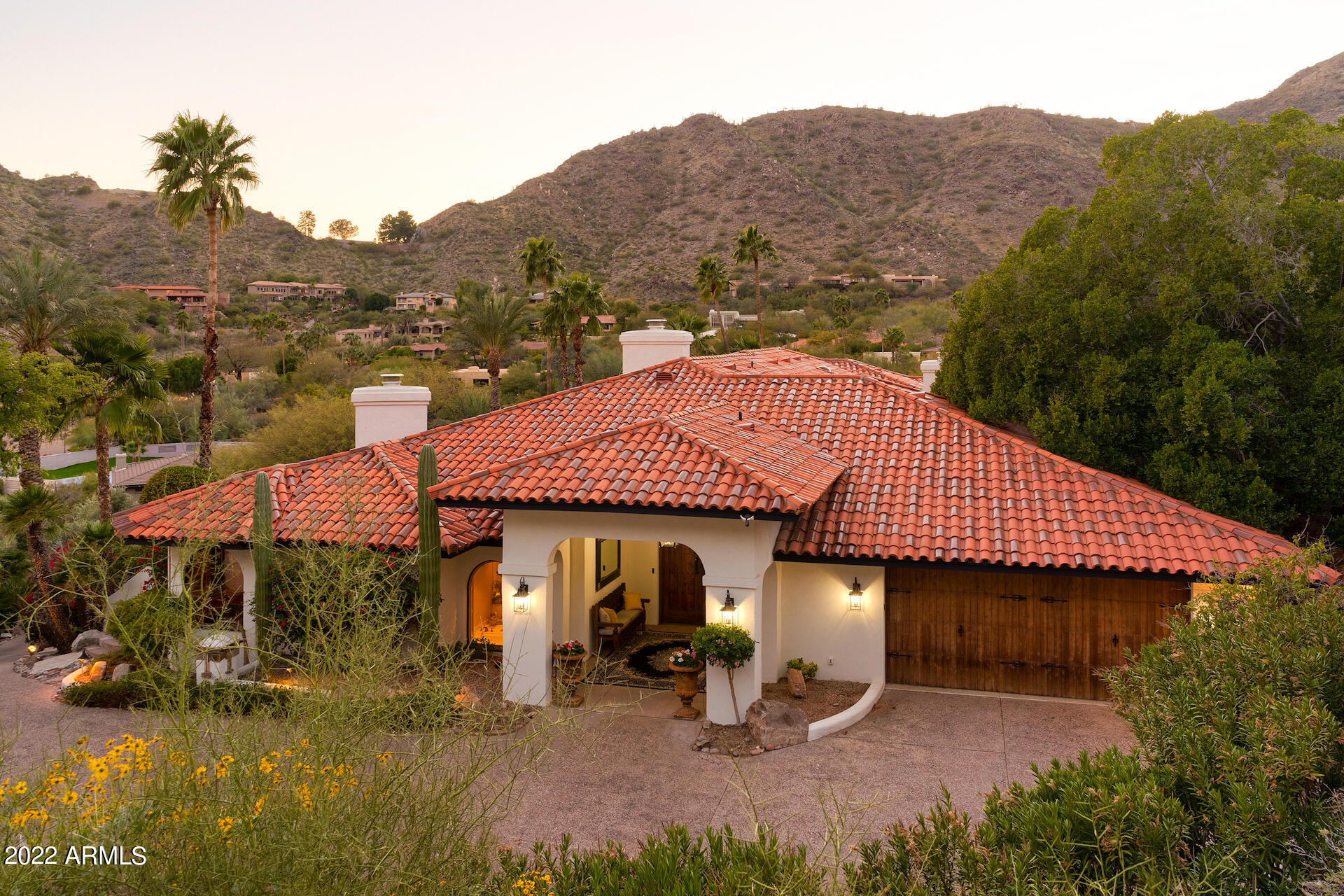 Rare single-level Move-in Ready Dave Hansen Mountaintop home. Totally Secluded with panoramic views of Camelback Mountain, Tatum Canyon and Scottsdale City Lights. Stunning private driveway lined with lush vegetation winds up to a dramatic entry carved into the Phx Mountain Preserve. Massive hand hewn entry doors reveal a 72 foot wide gallery hall with art lighting, artesian wood beams, rustic doors and hand forged iron accents leading to a showcase wine cellar. A plethora of amenities for the most discriminating owner includes 8 sets of arched French doors, 4 fireplaces, lush courtyards with soothing Canterra fountains. Designer Dominic Burda used an extensive south-facing window package to allow all primary rooms views of the Praying Monk-Camelback Mountain silhouette from this elevated perch cut into the mountainside.  Spectacular wrap-around covered patios offer warm and enchanting conversation niches enticing a great book or glass of wine with a friend. Beautiful white Gourmet kitchen, large pantry, Viking gas cooktop, xtra-wide Subzero. Owner's Suite features two generous Walk-in closets with skylights, one with island and chandelier. Spa bath with stunning chandelier over a polished silver clawfoot tub. Tub surrounded by a curved wall of French pane windows viewing lush, but private, panoramic views. BEGs for a Girls-Night-In! Bedroom was designed for front row views, and features built-in Cabinetry, Fireplace and a large sitting area. Wide hallway from the wine cellar leads to the Executive Office, lined with floor to ceiling bookshelves. Your desk faces spectacular panoramic views. Built-in credenza, cabinets, floor-to-ceiling bookshelves and supply closet. Doors allow breezes from covered patio, and outside access to front driveway for the occasional client drop in. 

Layout:  Could be 6 total bedrooms (3 ensuite) +office/library.  3 Ensuite bedrooms including Master. Family Room has another full bathroom, in addition to the Powder Room. Additional bedroom near Master is perfect for Nursery or Secondary Office, or could use ensuite bedroom bath across hall. No active HOA currently.   This prime lot was selected as the original Tatum Canyon Street of Dreams showcase, but its current lush vegetation required decades of loving garden maturation.  VERY secluded with some of the best private views available due to the terracing overlooking the pool & Patio below. Just enough grass for your doggie, but otherwise a low maintenance lush Acre+ Mountain Oasis.