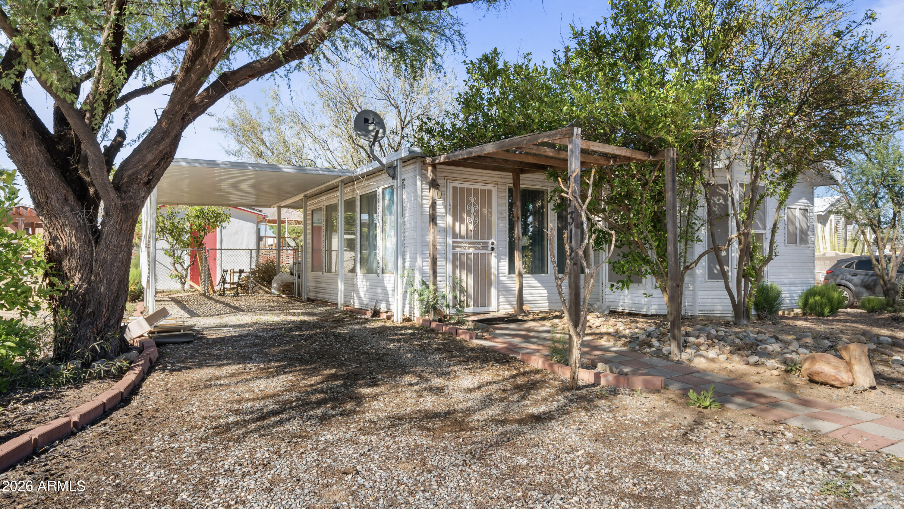 Affordable park model home located in a quiet desert community in Congress with scenic mountain views and a peaceful atmosphere. This cozy home offers approximately 628 square feet of living space, featuring a comfortable living room with plenty of room to relax and a kitchen with large windows that provide abundant natural light. The kitchen also includes a self-cleaning oven, adding convenience to everyday living. Recent upgrades include a new roof and a full solar system that provides free electricity, helping keep utility costs low and making the home more energy efficient. The property includes covered parking, a fully fenced backyard, and mature shade and citrus trees, creating a private outdoor space perfect for enjoying the desert climate. The low-maintenance desert landscaping makes the property easy to care for while still offering usable outdoor living space. Conveniently located with easy access to State Route 89, allowing for easy travel to Wickenburg, Prescott, and surrounding areas. Comfortable, cozy desert living in a welcoming community setting.
