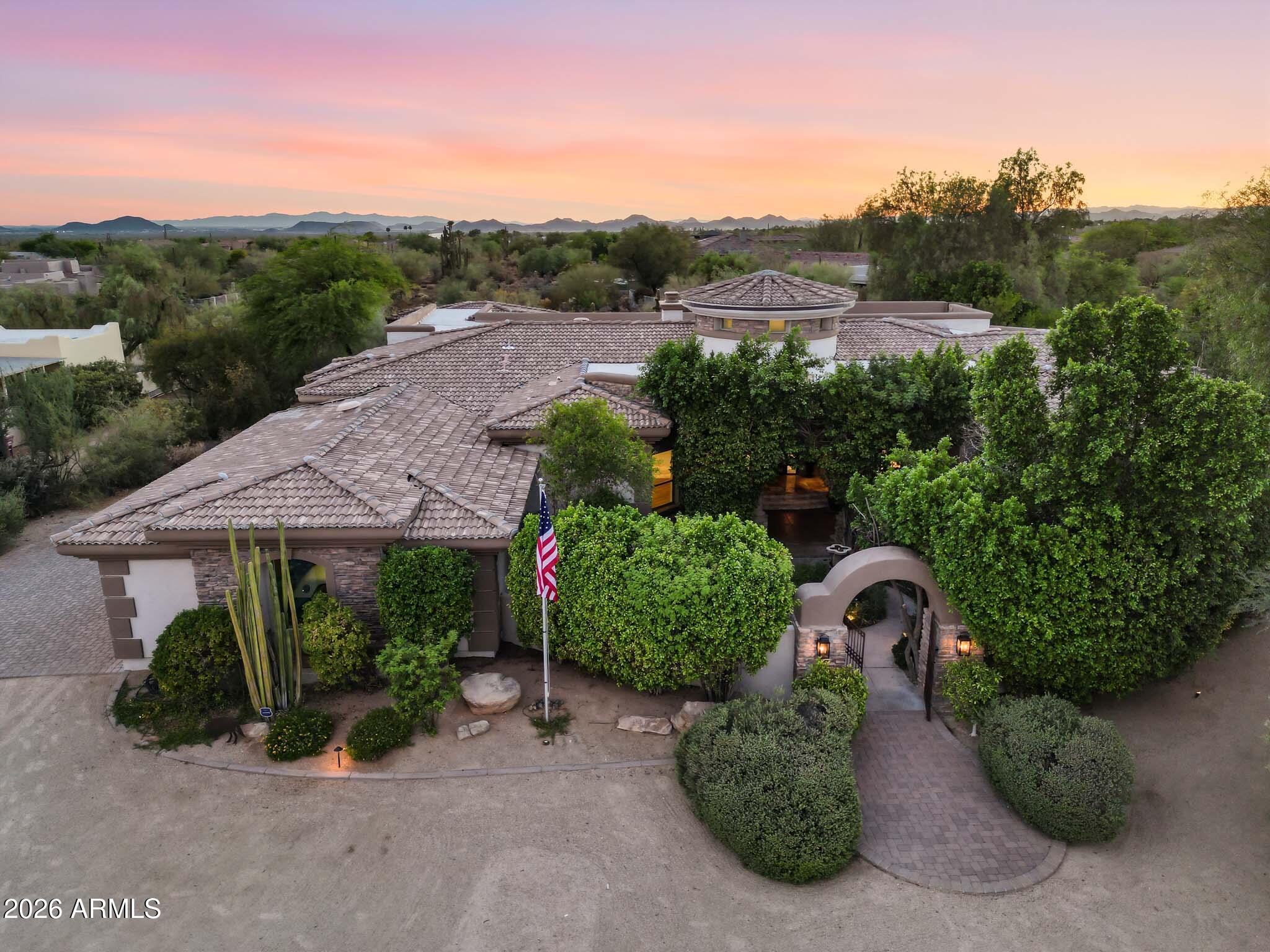 A rare opportunity to own a truly custom estate on just over one acre, where timeless craftsmanship, artisan details, and breathtaking Arizona scenery come together. From the moment you arrive, a circular driveway surrounded by mature Sonoran desert landscaping leads to a lush front courtyard with a tranquil fountain, setting the tone for this one-of-a-kind property.
Inside, the dramatic formal living space showcases a 22-foot coffered ceiling, elegant wet bar, and architectural radius windows that frame incredible mountain views while filling the home with natural light. Thoughtfully selected finishes include Bavarian Cherry hardwood floors, Turkish travertine, solid alder doors, custom alder cabinetry, solid cedar exterior doors, and custom glasswork by award-winning Southwest artist Bob Berg.
The private 485-square-foot guest house is connected by a breezeway and features its own iron door entrance from side yard, large living space, kitchenette, full bath, HVAC system, and water heater, creating endless flexibility for guests, multigenerational living, or a private retreat.
Designed to embrace Arizona's indoor-outdoor lifestyle, the backyard features a resort-style pool with water and fire features, separate spa, outdoor kitchen, and expansive sunken pergola with a wood-burning fireplace. A custom spiral staircase leads to a reinforced view deck capturing spectacular 360-degree views, unforgettable sunsets, and the surrounding mountain landscape.
With no HOA, exceptional privacy, no neighbors directly behind, premium custom details throughout, and a newer main HVAC system, this estate offers a level of character, craftsmanship, and setting rarely found.