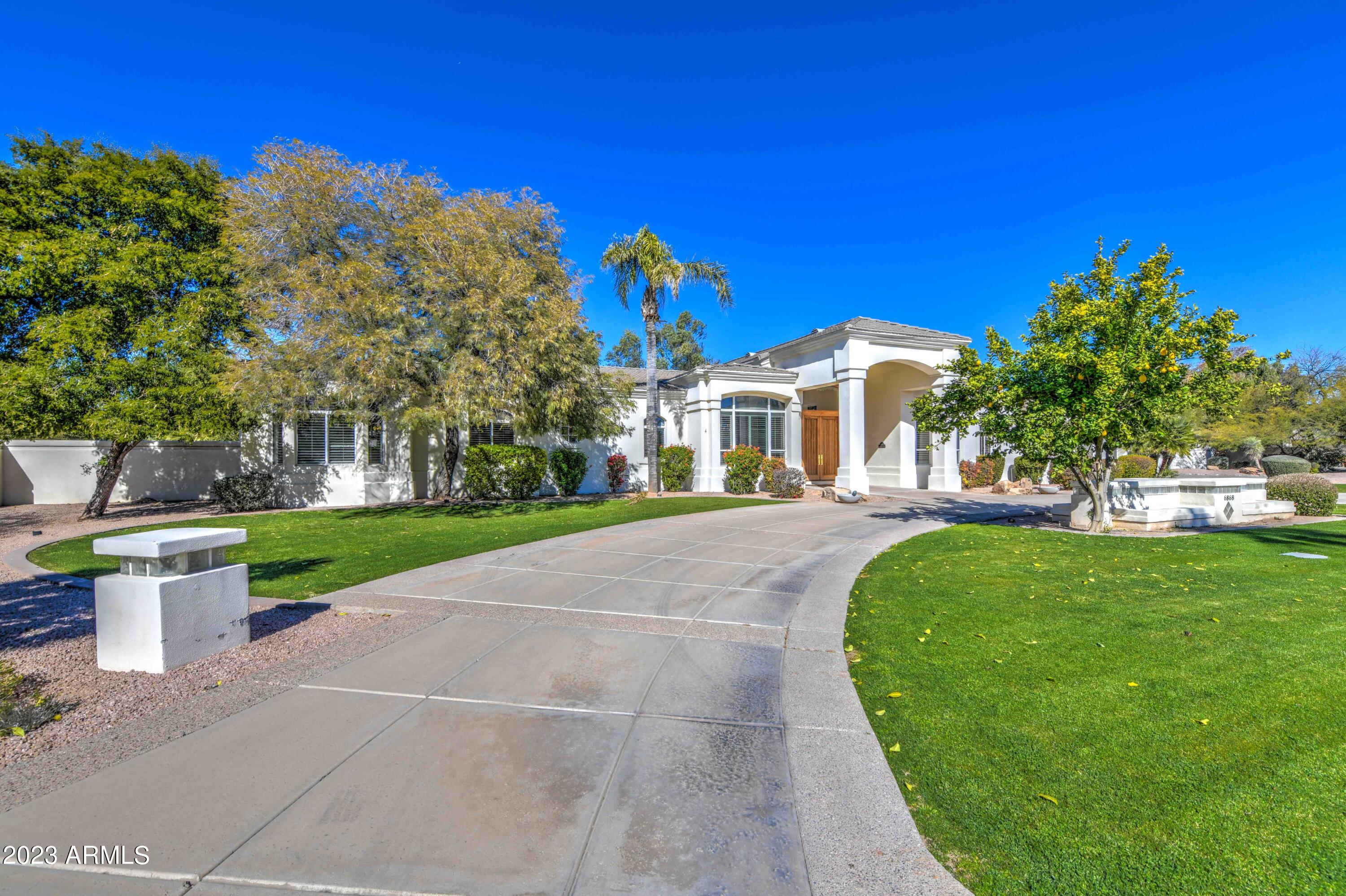 Welcome to your picturesque Paradise Valley home. From the second you pull up, you'll be charmed by the expansive lawn and circular driveway. Step inside to the formal dining and living rooms, with soaring ceilings and a wall of glass capturing backyard views. On to the kitchen, which flows into the family room with wet bar, the perfect place to entertain or for a relaxing evening at home. The ideal floor plan features the split master bedroom suite plus office in the east wing, with three guest bedrooms on the west wing, each with private bathroom. There are also two half bathrooms in the home. The back yard has space for everything, featuring a large party pool, plus grass and desert areas. With tons of golf, high-end shopping, & endless fine dining options nearby, this home has it all!