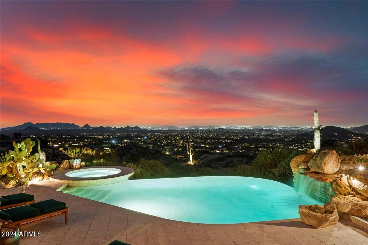 Experience unparalleled luxury with this extraordinary property—a masterpiece of worldly design and artistry. Nestled at the top of an elevated panoramic site in The Reserve at Apache Peak, this home is a true showpiece crafted by elite artisans, master craftsmen, and expert metal forgers. Sprawling over an expansive 7,500 square feet of living space every detail is a work of art, from the hand-carved wood, custom tile and stonework, and intricate mosaic art to forged metal accents, sparkling crystal chandeliers, and unique hand-painted murals. Stunning Venetian plaster walls, bespoke ceiling treatments with custom lighting, and whimsical touches create an elegant yet inviting Alcazar-inspired haven. Breathtaking vistas surround you from every corner of the property, while a thoughtful split floor plan offers privacy and comfort. The luxurious primary suite lies on one side, with two guest suites on the other, each designed with exceptional care. A separate guest house includes two additional ensuite bedrooms, a cozy den, a well-appointed kitchen, and a private patio, accessible by elevator from the garage or via a garden path. For leisure and entertainment, indulge in the billiards room with a wet bar or unwind by the tranquil fountain in the gated courtyard. A grand theater, complete with velvet curtains, surround sound, and oversized seating for eight, brings cinematic experiences to life. An elegant office nearby provides a quiet space for business needs. The formal living and dining areas invite relaxation with breathtaking views, a sunken wet bar, and a hand-carved Cantera stone fireplace. Step outside to the expansive patio, where you can enjoy alfresco dining, a heated pool, spa, and a soothing rock water feature. As evening falls, a softly illuminated desert path guides you to a secluded vantage point perfect for stargazing over the mountains and city lights as well as an in-ground fire feature with ample seating. Exclusive membership is available to the Desert Mountain Club and enhances the allure of this one-of-a-kind residence. Discover the ultimate blend of artistry, comfort, and mesmerizing scenery in a home that truly has it all.