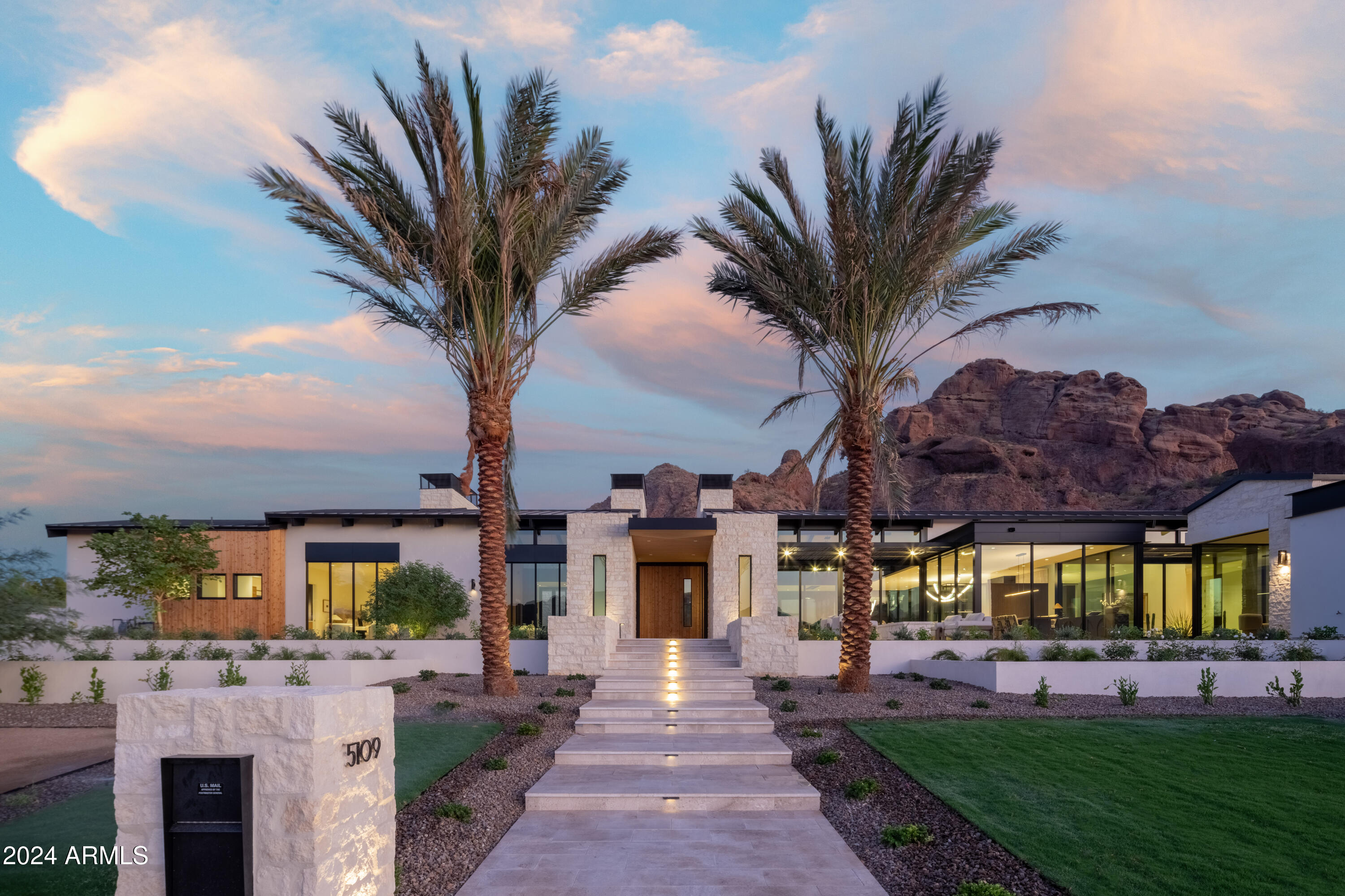This exceptional residence, the pride of Paradise Valley, provides breathtaking, unimpeded views of the mountains. It's a creation of Bedbrock Developers, recognized as the foremost luxury home builder in Paradise Valley. This magnificent home, architecturally designed by award winning Cosan Homes, principal Scott Carson, offers an expansive 7,558 square feet of living space, which includes a luxurious 1,265 square- foot, three room guesthouse, and is the epitome of elegance and luxury. Interiors designed by Kristin Hazen of Kristin Hazen Design, feature an open floor plan that includes a grand great room, a gourmet kitchen, back kitchen, gorgeous bar and recreation room. The masterful design and attention to detail are evident throughout the house bedrooms and five and a half bathrooms. The primary suite serves as a private retreat complete with a spa-like bathroom, his and hers walk-in closets, and a private patio overlooking Camelback Mountain and the serene backyard. Each additional bedroom is equally as impressive, featuring its own ensuite bathroom and walk in closet.
The outdoor living spaces, expertly designed by David Creech of CF Design, are as remarkable as the interior. Offering spectacular and unparalleled  360° panoramic views of Camelback Mountain, Mummy Mountain, Piestewa Peak, the property boasts a gorgeous pool, spa and ample space for entertaining. Architect Carson masterfully integrated glass walls and ceilings in order to maximize the breathtaking mountain vistas resulting in an abundance of natural light and seamless integration with the surrounding landscape. Located in the highly coveted Paradise Valley, this home is conveniently situated just moments away from world-class shopping, dining, and entertainment. It truly represents a rare and special property in an exceptional location.