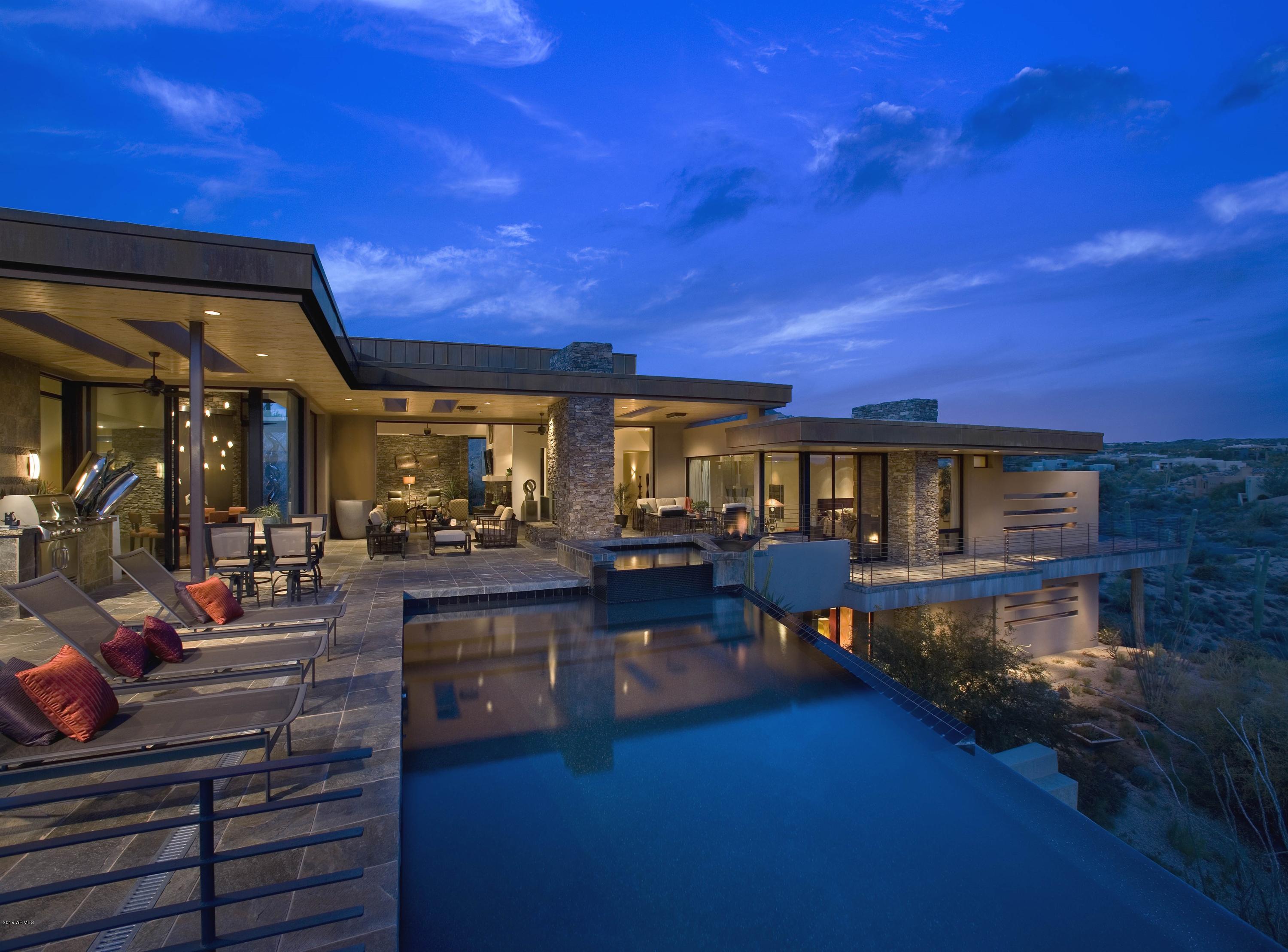 This exquisite home provides the perfect balance of warmth, intimacy and convenience.  Expansive glass walls and pocketing doors eliminate a distinction between the interior and exterior.  Designed by award winning H&S International architect Bing Hu, the home is inspired by Frank Lloyd Wright and is crafted to cascade down the site and is a perfect blend of Passion, Vision and Execution.  Overlooking starkly beautiful desert scenery from every room with sweeping views of mountains, sunsets and Valley views, this home 
is situated on over 5 acres providing the owners total privacy. 4 bedrooms, office, fitness room, entertainment room and 6 baths make for the perfect home for family and guests. Membership available through The Desert Mountain Club.