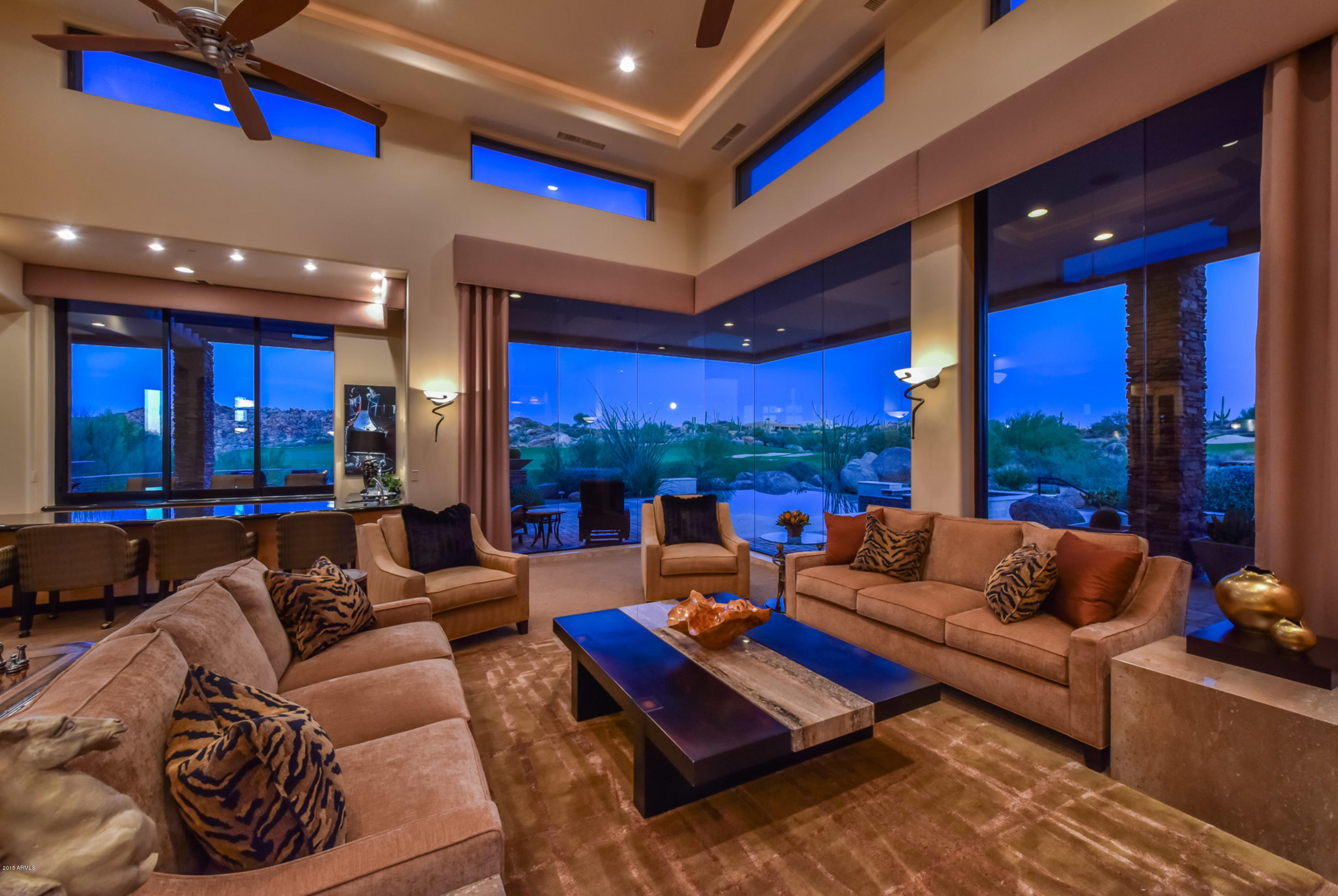Stunning desert contemporary on a premium lot located on the 10th hole of the prestigious Pinnacle Course at Troon North Golf Club. The negative edge pool and spa draw the eye to the amazing 180-degree golf course views. The expansive outdoor patios, including a fire pit, BBQ, fireplace, and multiple entertaining areas, allow for optimal use of the outdoors. With clean lines, dramatic lighting, and expansive use of glass windows and doors, this home is remarkable. The office is well appointed with box beam ceilings, wood flooring, and furniture quality built-ins and stacked stone fireplace. A spacious open floor plan, separate guest casita, master wing with an impressive master bath featuring its own exercise room, a gourmet kitchen and wet bar completes this custom built estate. i More detailed finishes include: designer carpet, glass and metal crafted entry door, slab granite surfaces, s/s appliances with a centerpiece hood vent, temperature controlled wine room.