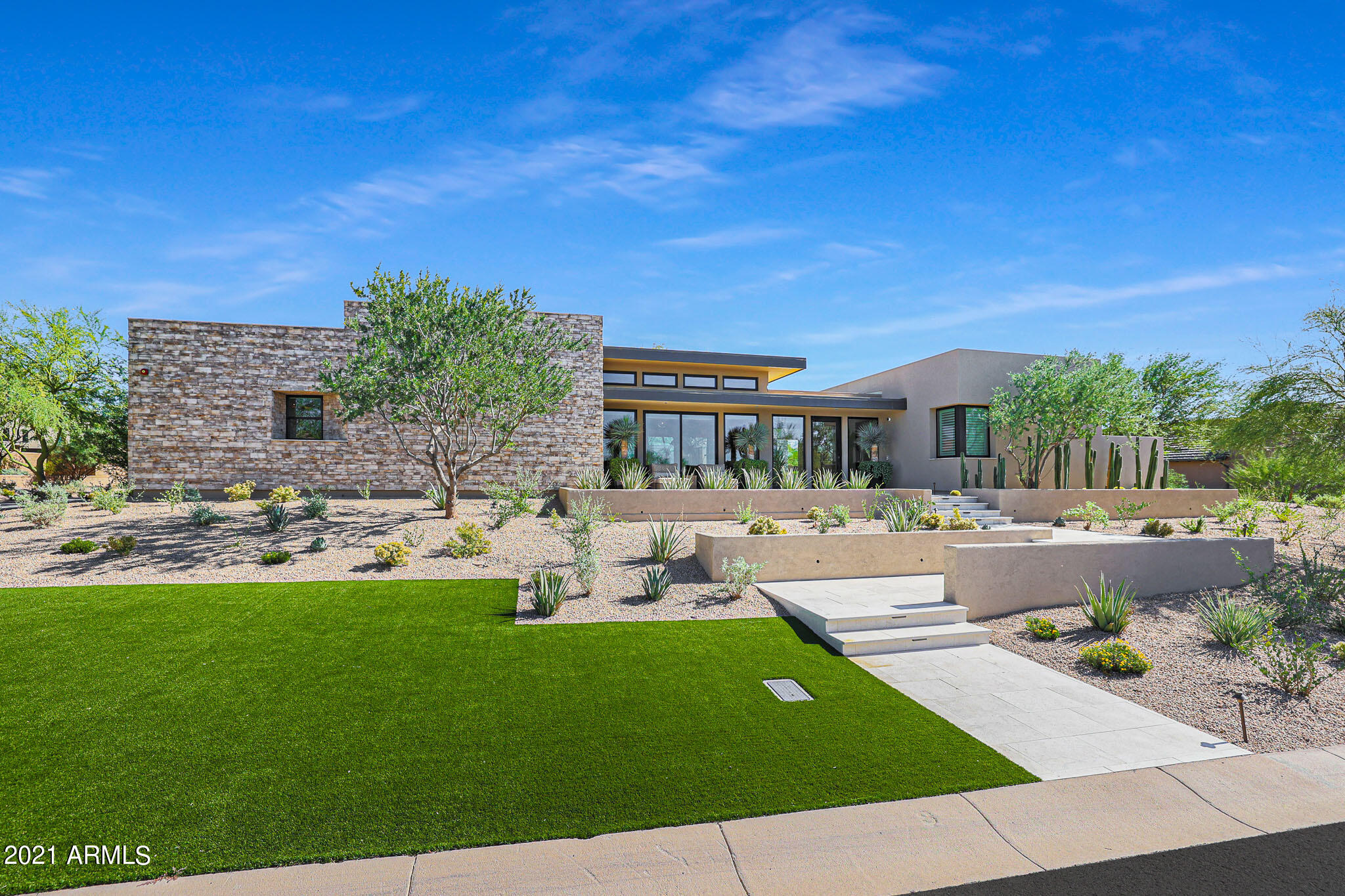 Arizona's most awarded luxury builder 2020-21. This amazing, gated community brings together vibrant, award winning contemporary design with seamless indoor-outdoor living. Explore the stunning desert surroundings just minutes from N. Scottsdale's finest dining and shopping destinations. This incredible contemporary home offers timeless indoor-outdoor appeal, all in a highly desirable location, with Mt. and city views.  Enter the keyless port e cochere and bring you and your guests into the inviting and unique courtyard. Over 3000 sf of outdoor living space with 2 massive ironwood trees and manicured desert landscaping. Stone, steel, glass and stucco complement this impressive luxury home. Single level, 6024 Sf of livable interior features the best of high end luxury at your convenience, from Wolf & Subzero, 200 bottle wine cooler, Wolf outdoor grill with built in cabinets, surround system throughout.  Waterfall island in kitchen, gorgeous stacked stone accent walls, stone floor to ceiling fireplace, tongue and groove wood ceilings in the entry, great room and master suite. Three interior bedrooms with in suite bathrooms. Guest quarters with separate entrance, in suite bathroom and washer/dryer hookup.
Office with a city view! Grass cloth wallpaper and built-ins. Mechanical window treatments for privacy.
Bringing indoors to outdoors with 6 sets of stackable glass walls that open up to the courtyard and patios throughout the home.
Laundry room features dual stacked washer & dryers, beautiful cabinetry and large center island. Entertaining flex room features dual water fall bar with under counter fridge, ice maker, sink and 5 tv's to view your favorite sporting events.
The master suite are what dreams are made of.  Take a shower or bath indoors or open the wall of glass and take one outdoors if you dare!  Enjoy the private spa, three sided negative edge pool and cold plunge, too.  Feel like you're at a resort everyday.  Come see this outstanding luxury home for yourself.