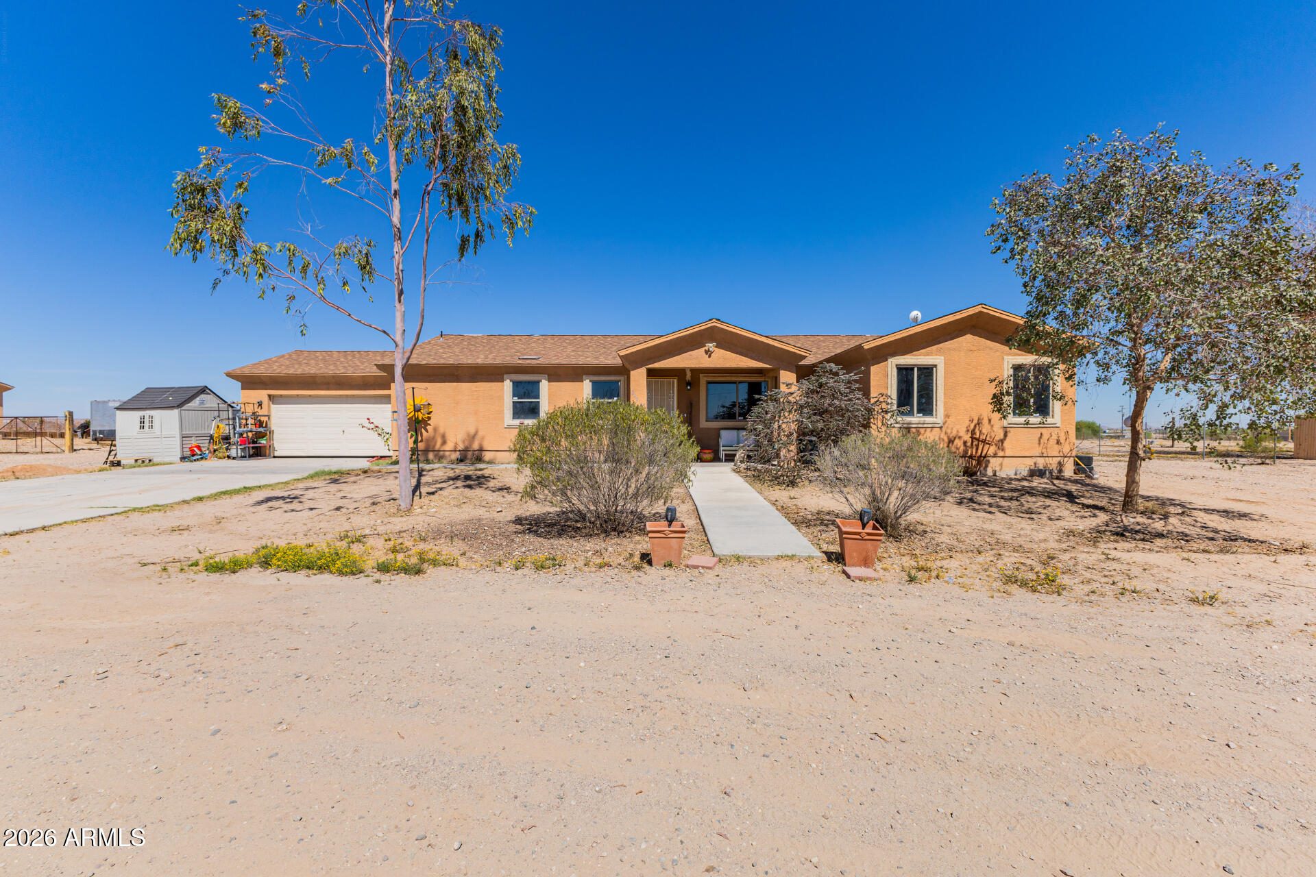You pull up the driveway and it's quiet - no traffic noise, just open space and mountain views in the distance. The walkway leads you to the front door, and right away the layout makes sense. It's a split floor plan, so everything feels open without everyone being on top of each other. Inside flows easily and you can really see the potential to make it your own - but it's what's outside that really changes how you live here. Out back, the space opens up to a fully fenced yard with mature trees that have been there a while - real shade, not the kind you have to wait years for. There's room to move, room to add, or just room to breathe. If you've been thinking about having animals, it's already set up: two horse stalls, a chicken coop, and additional space for other livestock. You can picture mornings out here, taking care of animals, or evenings on the concrete patio when everything settles down and the mountains start to change color. The practical pieces are already handled too. There's a newer HVAC system in place, a shared well to help keep costs down, and a two car garage plus a four car driveway with plenty of space for vehicles, trailers, or toys. It's not just about having land - it's about actually using it. And this is the kind of place where that feels easy.