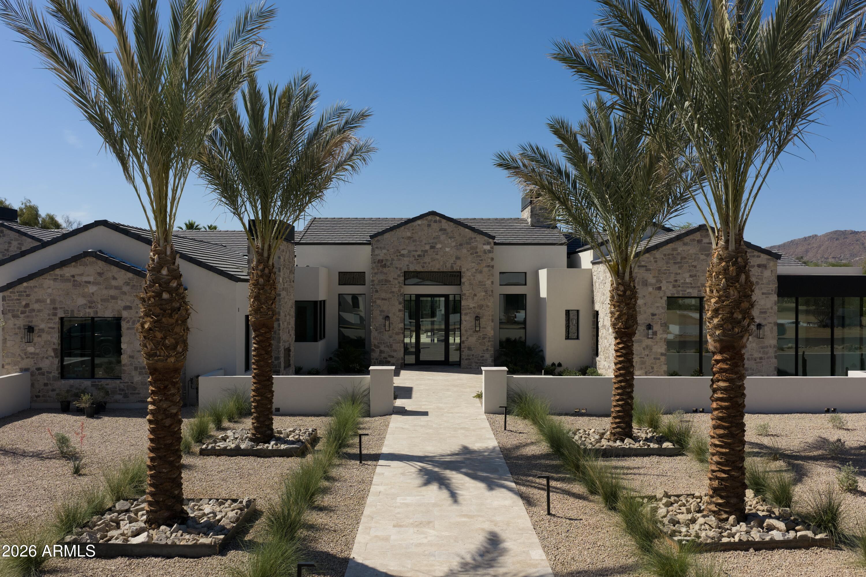 Welcome to 7301 N Mockingbird Ln. A 9,052 sq ft new build on over an acre in Paradise Valley. Completion May 2026. Set on over an acre this custom estate blends modern scale with natural materials.

The floor plan is designed for grand-scale entertaining and comfortable daily living. The main area features a sprawling great room that flows into a morning room and formal dining space. The chef's kitchen is equipped with dual islands, a walk-in pantry, and a fully outfitted butler's pantry. A custom bar and private game room provide additional spaces for hosting.

The estate offers five bedrooms and five full bathrooms, plus powder and pool baths in the main home plus a detached guest home with an additional full bedroom and bathroom. The primary suite is a private sanctuary with a firep and expansive walk-in closet. Guests are accommodated in a detached wing featuring a living room, full bathroom, and bedroom suite.

Outside, the 48,302-square-foot lot maximizes the Arizona lifestyle. The resort-style backyard centers around a large pool and spa, complemented by a custom ramada and a full outdoor kitchen. The property includes dual two-car garages connected by a beautiful privately gated motor-court.