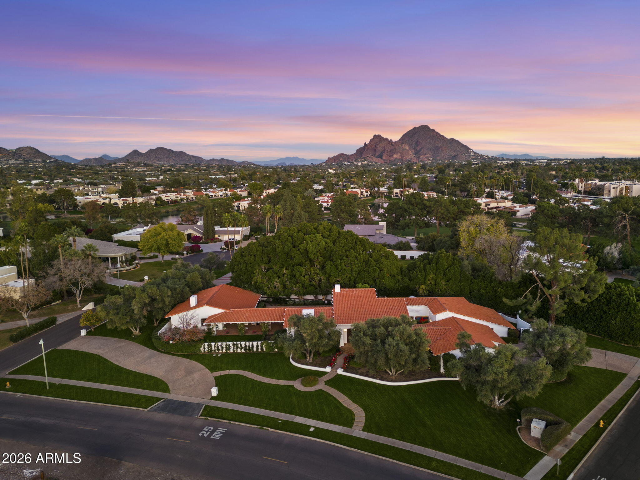 Perched on a commanding 1.1-acre elevated lot in Arizona's coveted Biltmore Estates, this exceptional Santa Barbara style estate offers an unparalleled blend of privacy, architectural refinement, and resort-style living. Surrounded by mountain vistas and just moments from the iconic Biltmore Hotel, the property is immersed in one of the most exclusive neighborhoods in the United States sitting directly across from two world-class golf courses and is adjacent to scenic walking, running, and cycling paths. Sprawling over 7,000 square feet this home offers 6 bedrooms and 5.5 baths with multiple flex rooms. The main residence is thoughtfully composed to balance grand entertaining with everyday comfort. Dramatic 25-foot cathedral ceilings and expansive picture windows flood the interiors with natural light, creating a seamless connection to the surrounding landscape. Public living spaces are elegantly positioned in the north wing and include a formal living room, dining room, garden room, and chef's kitcheneach designed with generous proportions and timeless appeal. The private south wing serves as a tranquil retreat, anchored by a luxurious primary suite featuring a full bath, spa-style shower, private dressing lounge, and bar. Three additional spacious bedroomsone ensuite and two sharing a beautifully appointed bathoffer comfort and privacy. A versatile recreation room with direct patio access completes this wing, ideal for leisure or wellness pursuits. Upstairs, a loft-style bonus room opens to a balcony overlooking the pool, mature ficus trees, and distant mountain peaksan inspiring space for work, relaxation, or creative pursuits. Equally impressive, the guest house is a private sanctuary of its own. It features a welcoming living room with fireplace, a well-appointed kitchen and breakfast area, and sun-filled picture windows framing mature olive and citrus trees. Two generously sized bedrooms provide serene accommodations, each with a full bathone offering picturesque views of the loggia, pool, and lush grounds. Designed for effortless indoor-outdoor living, this remarkable estate is equally suited for refined gatherings or casual enjoyment, with fluid spaces that invite connection, relaxation, and celebration in one of the nation's most prestigious enclaves.