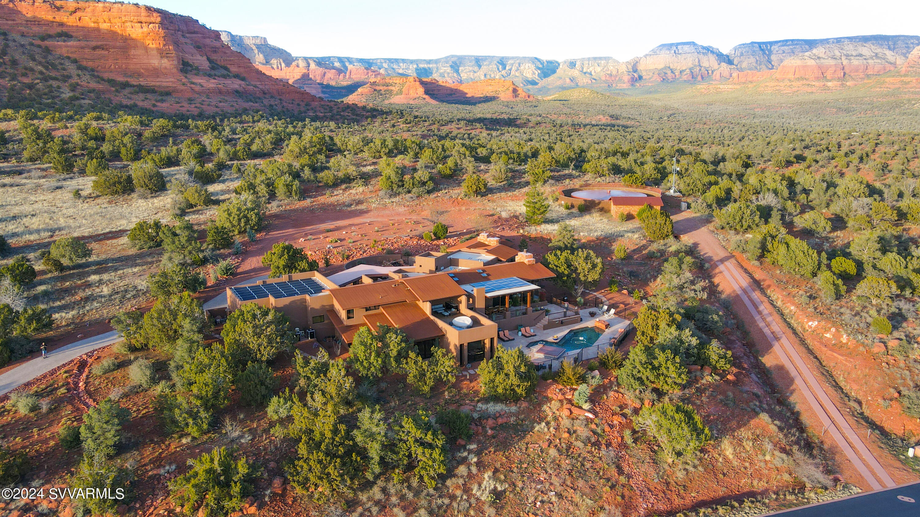 Using the red rock landscape as LIVING ART this architect-designed gem rests atop 2.13 acres on national forest.  Designed for Sedona's indoor-outdoor living with the 4,700 s.f. main home + 1,000 s.f. guest suite, all against a 360-degree red rock backdrop. The great room is a celebration of this landscape, with a design that prioritizes the connection between inside and out: living spaces spill seamlessly outside. Over $200,000 was invested in landscaped grounds which complement the energy savings of a 15.2 KW solar system serving the pool & home comfort  with radiant floor heat. The chef's kitchen is Wolf/Sub-Zero, with leather texture finish granite counters. Views envelop the primary suite with a double-sided fireplace, stone shower & Venetian stucco bath. Saltwater pool & jacuzzi. With gallery-like view spaces the artfully placed and expansive windows invite the Sedona red rock landscape inside to create "living art" within the home that changes throughout the year with the seasons. Surrounding decks, patios and courtyards further immerse the owners into nature at its very finest.

Features and Amenities:
-The estate backs to the national forest, offering unparalleled privacy and surrounding natural beauty.
-Enjoy the continuity and ease of indoor-outdoor resort-style living with all the amenities of a fitness space, pool and jacuzzi, meditation loft, and walking access to hiking trails.
-Experience the connection to the native environment and views that imbue calm and serenity.
-Driveway entry features a stacked red rock planter with large Juniper Tree and Iris Garden, of the original homestead highlighting unique, original rock work.
-Stacked stone pillar, covered walkway connects the garage to the front entry, highlighted by tongue and groove finish.
-Main entrance is adorned with a solid, Basalt Stone bubbling water feature illuminating beautifully in the evening.
-Grand, custom mortar and flagstone floors grace the primary living spaces indoors and out, promoting a seamless connection to nature.
-Impeccably designed interior highlighted by a rain chandelier, by Restoration Hardware, in the foyer and over expansive dining room table.
-Great room floor-to-ceiling stacked stone fireplace highlights large boulders at the base and mantle, preserved from the property providing continuity to original build site.
-Enclosed courtyard accessible from the Formal Dining Area provides striking views of Doe Mountain, a tiered, rock water feature, custom rusted iron fencing and gates, and a hand-made John Unger Big Bowl O'Zen Sculptural Firebowl.
-Stunning Western Windows and exterior door package throughout
-Chef's Kitchen includes a 48" Sub Zero refrigerator, 6 burner Wolf range with separate induction cooktop, wall convection/steam oven and microwave.
-A walk-in pantry hosts additional refrigeration and freezer units and ample storage.
-Spacious and wrapped in red rock views, the leather-finished granite countertops, eat-in bar seating, and custom cabinetry with Restoration Hardware fixtures.
-The Primary Bedroom offers an intimate escape with a dual-sided fireplace that may be enjoyed from both the bedroom and attached bathroom.
-Wake up and enjoy panoramic red rock views as you start your day.
-The luxurious Primary Bath features Val d'Orcia Quartzite counter surfaces, a soaking tub nestled beside the double-sided gas fireplace, and a custom glass-to-glass corner window shower.
-Wall finishes feature custom Venetian Plaster with unique copper inlaid patterning.
-Thoughtful details include custom solar window shades, Grohe faucets, Toto toilets, and Kohler bathtubs throughout.
-Enjoy indoor-outdoor living on the upper Trex topped deck with shaded seating perfect for stargazing or simply admiring the expansive views.
- Enjoy alfresco entertaining year-round under the large covered patio accessible off the kitchen and main living space. Amenities include outdoor Wolf built-in barbecue, countertops and large TV.
-Resort-style saltwater pool and jacuzzi with an art-crafted, angular spillway, electric or propane heating.
-A captivating custom-made iron fire bowl (Great Bowl O'Fire) by artist John Unger creates dances of light at sunset.
-Guest Casita offers a unique living space and privacy, kitchenette, and access to the pool area.
-The Casita provides access to the exercise room, pool table room, wine storage, and extra secure storage.
-The home overlooks Aerie Lake and breathtaking surroundings are enjoyed from various outdoor spaces.
-Added sensory stimulation is derived from the intricate landscaping featuring mature trees and native, fragrant, flora.
-Spacious and oversized, attached 3-car garage with epoxy flooring, utility sink, and solar equipment access.
-The fully landscaped grounds include multiple Japanese Maple Trees, numerous fruit trees, large cactus garden, and prominent Lyman Whitaker Garden of Ginger sculpture from the Renee Taylor Gallery in the main entrance garden.
-Radiant floor heating with four control zones ensures cozy warmth in every corner.
-15.2 KW solar panel system powers the home efficiently, featuring flat panels and tilted panels for optimal energy generation.
-Security system extends throughout the property for peace of mind.
-Expertly landscaped by top professionals with an investment of $250,000.