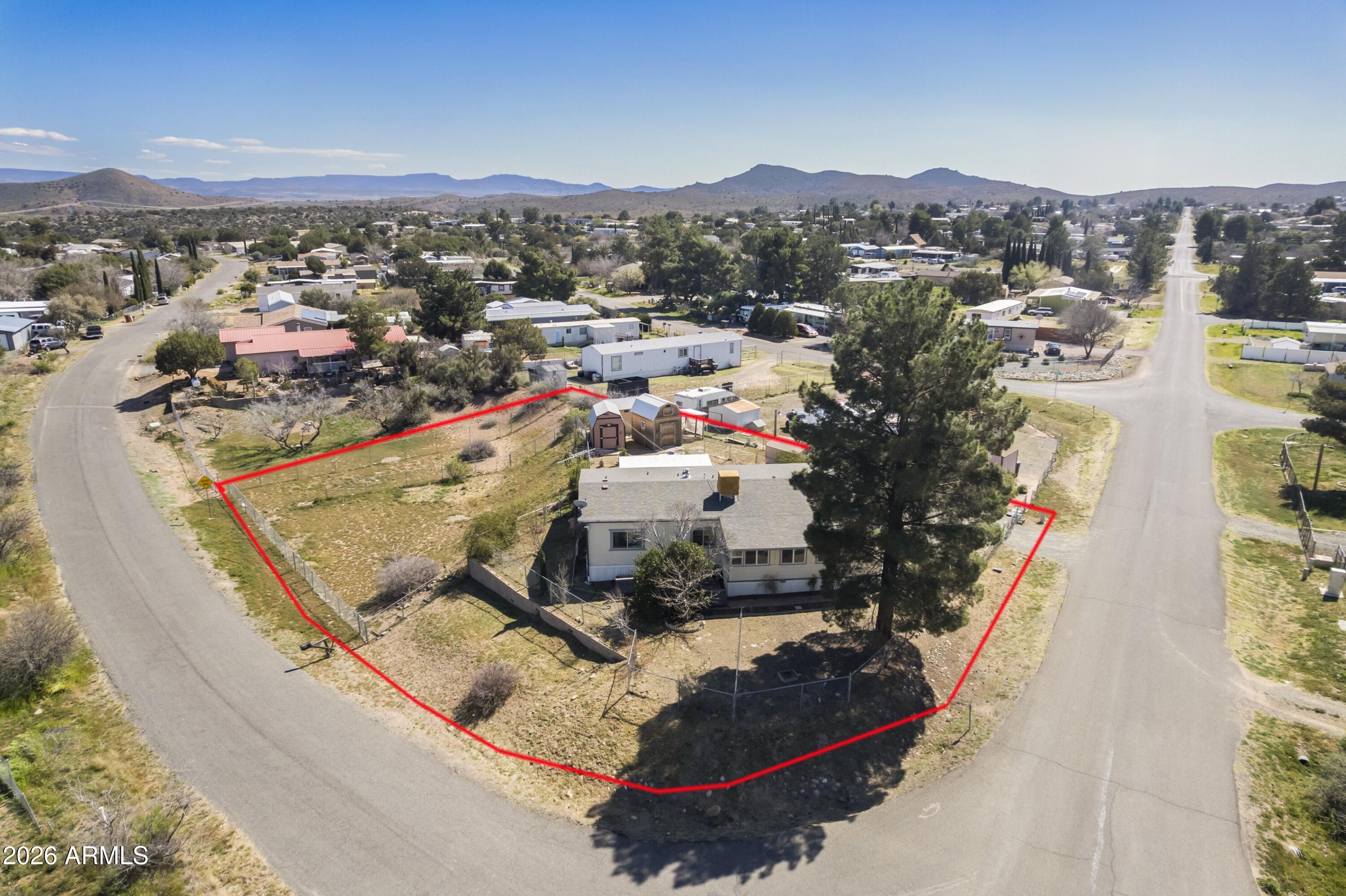 This spacious 1702 sf home offers 2+ bedrooms, 2 bathrooms on a Large .42 acre Corner lot with double gates on lower portion for easy access to park all of your work trailers, toys and or your RV. Home has an addition on the back with 3 additional rooms with potential 3rd bedroom and/or an extra-large closet, den or office. Evaporative Cooler, windows & Kitchen cabinets were replaced in 2020 along with butcher block counters. The lot is fully fenced with chain-link on both the upper & lower portions & has several fruit trees: Pear, Plum, Nectarine & Fig along with 2 Grape Vines. There are 4 storage sheds to accommodate your tools, garden supplies and or make it your own she shed or man cave.  An additional sitting area with windows in the back and a sunroom on the front makes it easy to... enjoy the beautiful weather. Centrally located to Prescott, Phoenix, the Verde Valley & Flagstaff to make for easier commutes. **NOTE ~ Fenced Lot below is part of the property!!! Seller is motivated!  Bring your offer!