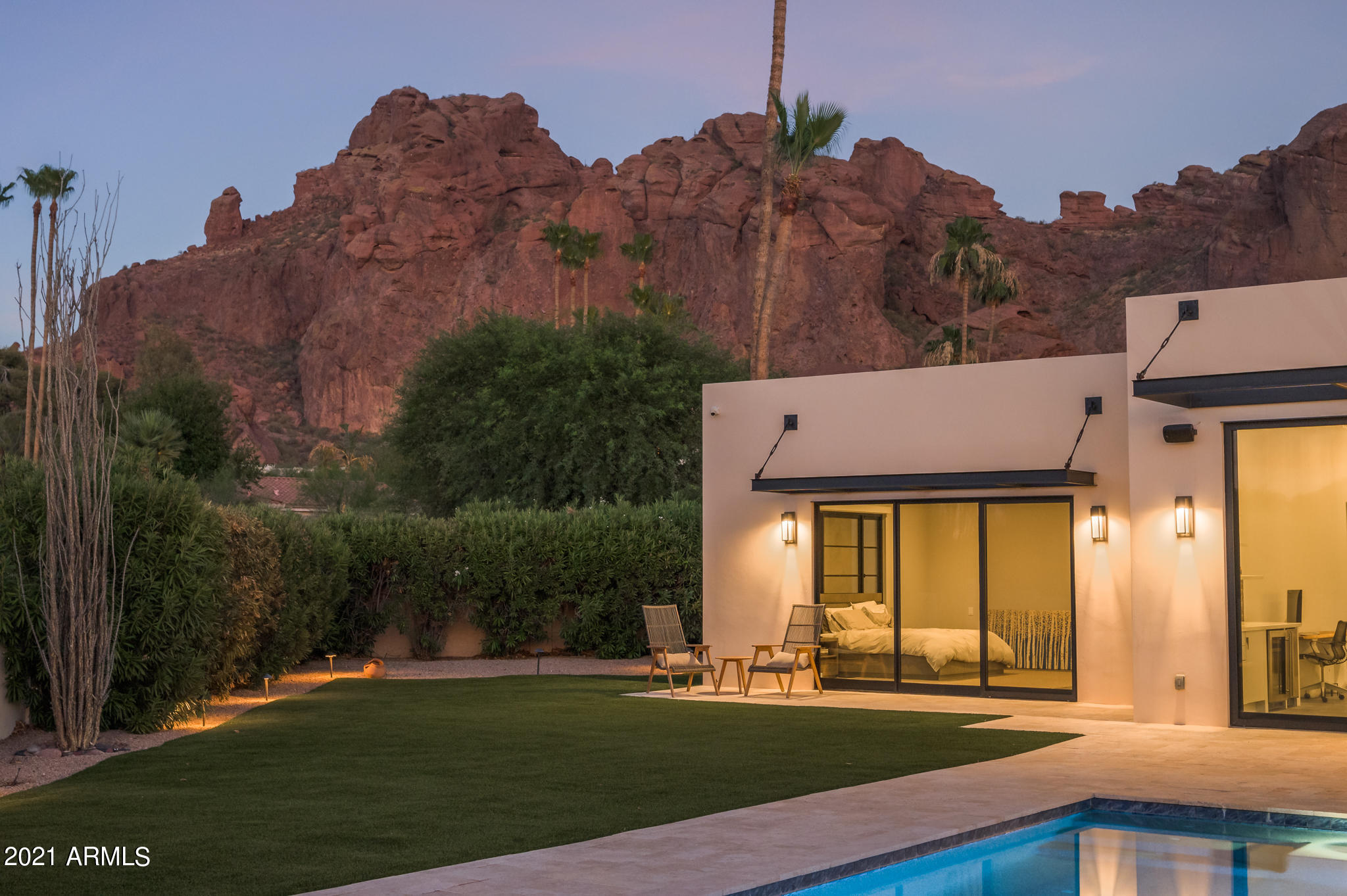Nestled at the base of Camelback Mountain, this striking property is the epitome of casual, cool and contemporary Arizona living. Architectural angles anchor the design inside and out, imbuing a sleek and modern feel. Featuring an open and airy floor plan, this impressive and welcoming single-level home is designed to optimize space, light and functionality. The versatile living spaces feature a double-sided fireplace, chef's kitchen and an impressive on-display wine cellar, all accented by exceptional finishes and luxury accents. Expansive glass doors lead from the living room to resort-like grounds that include a pool, lounge seating and a gourmet grilling area. This premium location offers fabulous city skyline and Camelback mountain views.