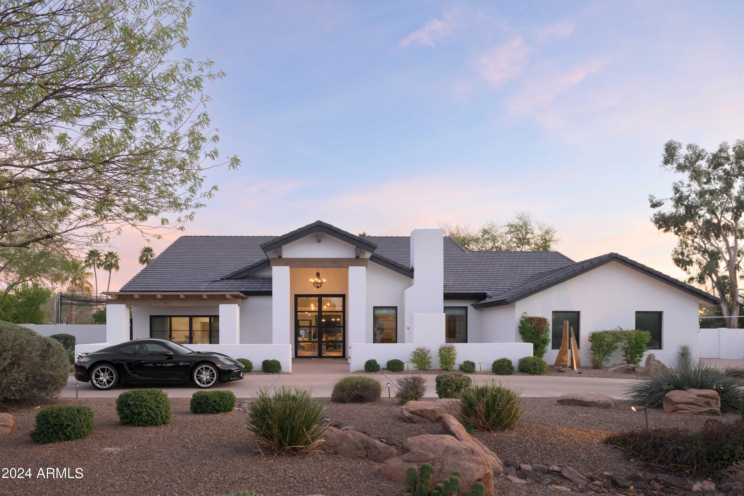 Phenomenal opportunity to own this newly reimagined & perfectly designed estate located behind the 24 hour guarded gate in Equestrian Manor. Sitting on a corner 3/4 acre lot, this magazine worthy property is beyond impressive from the circular driveway, past the outdoor fireplace, through the bright entry foyer to the enviable resort style backyard. Every high-end design detail was executed by Emily Yeates of Urban Revival creating a modern yet functional aesthetic in this 4 bedroom 3.5 bath home. Brand new architectural shingle roof, smooth stucco exterior, paint, black metal clad Anderson windows & doors, wet bar, engineered hard wood floors, designer tile flooring, designer fabric window coverings, chandeliers, plumbing fixtures, wallpaper, Batting Cage & Sport Court. The custom metal clad entry door invites you into a bright foyer which showcases a vaulted ceiling, modern brass chandelier & new staircase. Off the foyer sits a vaulted Living Room with marble enclosed gas fireplace, chandelier & automatic designer shades for privacy. The downstairs Primary Suite features a vaulted Office with access thru new Anderson sliders to the beautiful front porch outdoor gas fireplace. Beyond the Office is a private spacious Primary Bedroom & Primary Bathroom with dual sink vanity, custom marble countertop, separate walk-in shower & bathtub, walk-in closet & extra storage plus access to backyard covered patio.The Family Room just beyond the Foyer offers even more entertaining space. Gather around the newly designed wet bar with SubZero beverage fridge, wine fridge & Scotsman ice maker or sit by the wall mounted Dimplex gas fireplace with quartz surround. Another Office located downstairs overlooks the stunning Dining Room & steals mountain views from the Kitchen portrait window. The Kitchen offers everything you could want including SubZero stainless fridge, Wolf wall mounted oven & microwave, Wolf gas burner cook top, vent hood, Asko dishwasher, new marble countertops, designer backsplash, pendant lights, leather cabinet pulls on the freshly painted cabinetry, new electric skylight & portrait window. You'll fall in love with the two sets of LG washers & dryers in the efficient laundry room. New marble tile floors, designer cabinet doors, marble countertop, extra storage & custom dog kennel area off the air conditioned 3 car garage. Powder Room downstairs with grass cloth wallpaper, floating marble sink, new gray marble subway tile floors. The newly built staircase with custom lighting takes you to the second floor where the views are unmatched. Two spacious bedrooms, one en-suite, a new Bathroom plus a Teen Room complete this functional floorplan. The teen room is your upstairs media room fit with it's own built-in counter & SubZero beverage fridge. Don't miss the upstairs balcony with amazing views & seating overlooking the backyard for the most discerning entertainer. Invite your friends to experience this beautifully landscaped resort backyard with expansive L-shaped covered patio, gas fireplace with seating, grotto style pool, spa, two round gas firepits with seating, speakers, surround souns, outdoor kitchen, BBQ, pizza oven, new Green Egg, freshly turfed putting green, new Batting Cage & new Sport Court. Backyard shed for extra storage. The 3 car garage is air conditioned & offers large storage closet. RV gate. Solar panels for efficiency. This estate is a true gem you will never want to leave!