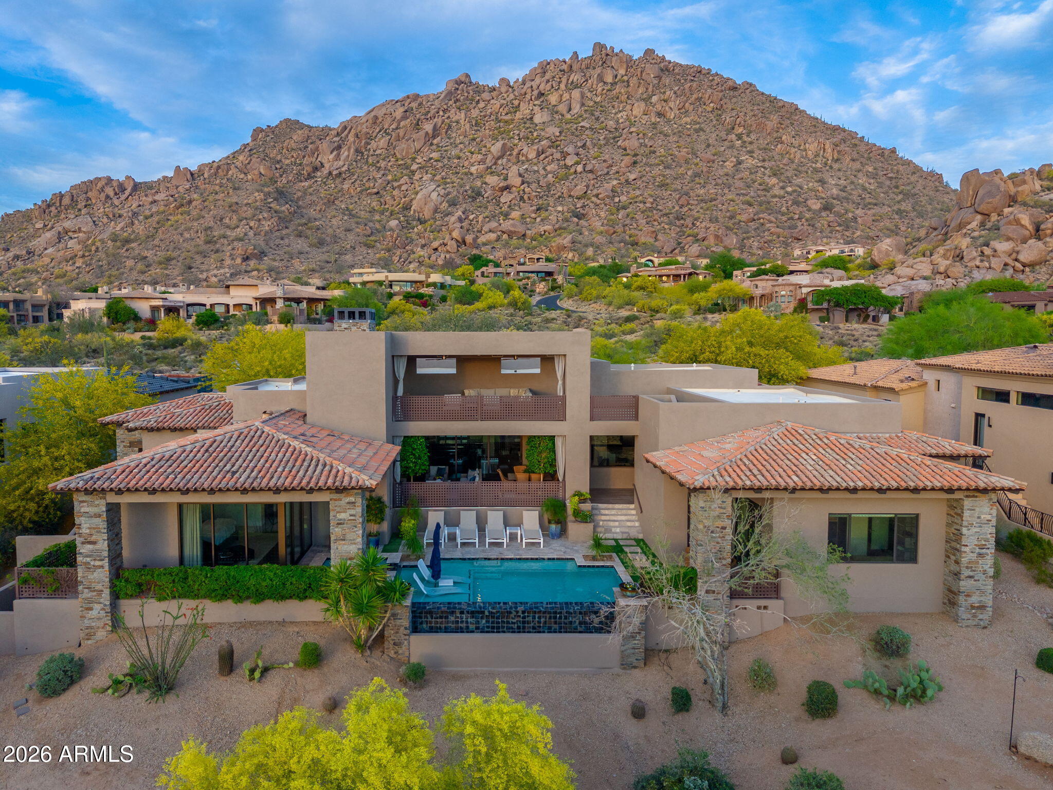 Welcome to this stunning estate located in the prestigious gated community of Artesano at Troon Canyon. Behind the manned guard gate and a second private gate sits this beautiful custom home tucked against the boulders of Troon Mountain, with panoramic city light and mountain views. Residents enjoy unmatched privacy, 24/7 security and close proximity to championship golf, scenic hiking, and all the best of North Scottsdale. This exceptional home is a masterpiece of elegance and functionality, offering a lifestyle tailored for entertaining. The estate offers three spacious and well-appointed ensuite bedrooms, providing comfort and privacy for all plus an oversized den, perfect for an office or a cozy retreat. The primary suite has expanding sliders that open to the pool/spa and offer beautiful views of the mountains and city lights. Pamper yourself in the spa-like master bathroom or enjoy the privacy of the separate outdoor garden shower. Luxurious amenities await, including a stunning chef's kitchen with a waterfall island. The great room features a 20ft sliding pocket door that extends into the large outdoor living space. The upstairs patio showcases breathtaking city views. Don't miss this opportunity to call this exquisite property your own.