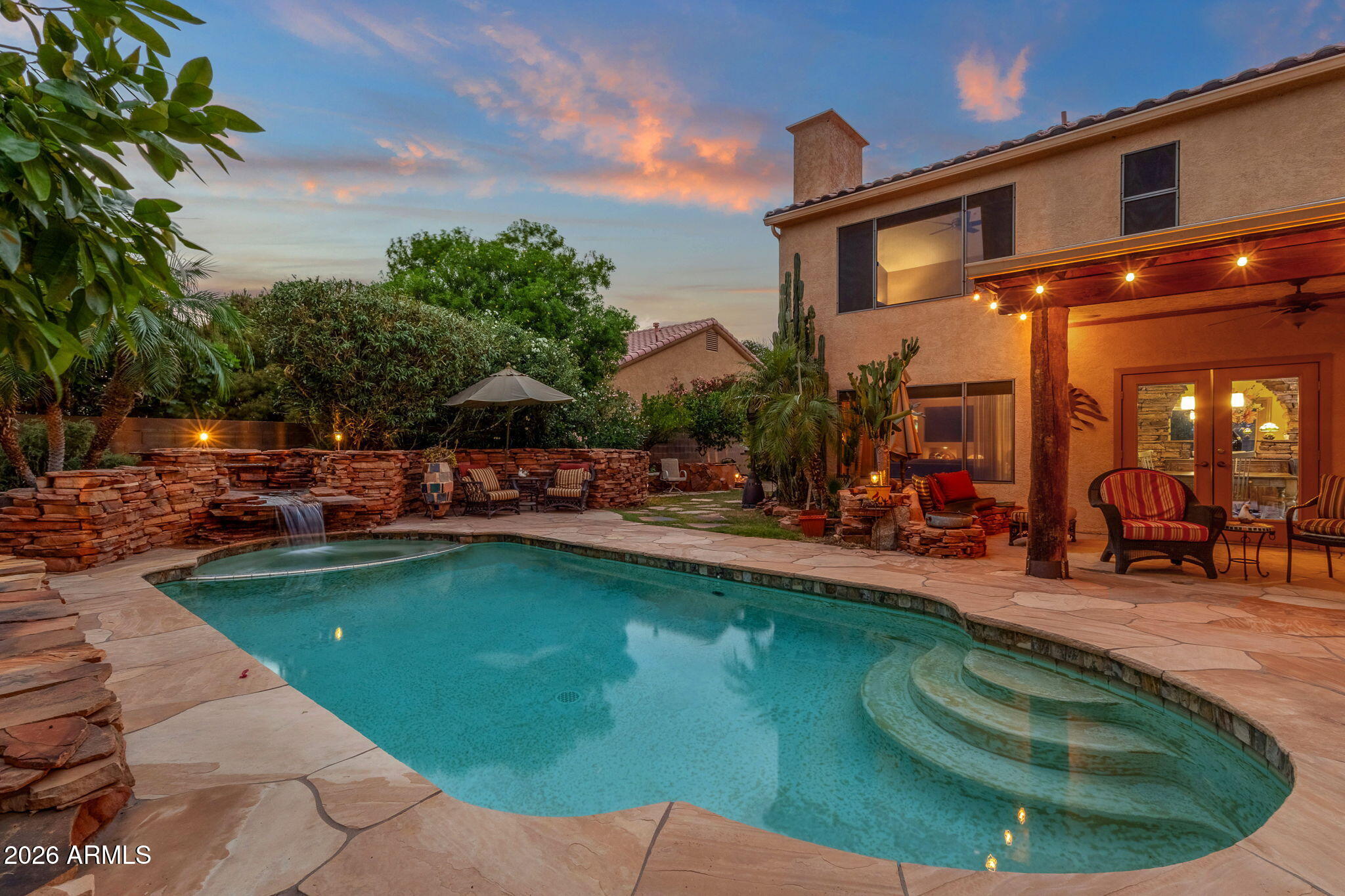 Located in Scottsdale's Desert Sage subdivision, this updated 4 bed, 3 bath, 2,438 sq ft home offers a flexible indoor-outdoor layout on an oversized lot with a standout backyard retreat with lush, mature landscaping. The kitchen features granite countertops, stainless steel appliances, rich wood cabinetry, island seating and direct access to the patio. Formal living and dining areas feature vaulted ceilings, tile flooring, arched windows and backyard views. The family room includes a stone fireplace, custom built-ins, display niches and warm Southwest-style finishes. The floor plan includes 3 bedrooms upstairs plus a downstairs bedroom, full bath and large office/den, offering options for guests, work-from-home space, hobbies or media use. The south-facing lush, backyard is designed for outdoor living with a pool, flagstone patio, grass area, mature palms, citrus trees, lush landscaping and multiple seating areas. Custom stonework creates a resort-style setting with built-in BBQ, artisan Italian pizza oven, outdoor fireplace/fire feature, juniper wood bar top, covered patio, string-light pergola area and a one-of-a-kind juniper 2-person swing. The primary suite includes vaulted ceilings, large window views and an updated bath with dual-sink granite vanity, soaking tub and separate glass-enclosed shower. Professionally designed boulder and stone landscaping adds character front and back. Prime North Scottsdale location with convenient access to shopping, dining, parks and Loop 101. Approx. 0.4 mi to Horizon Park and Horizon Dog Park, 0.2 mi to nearby restaurants including Streets of New York, Subway and Ono Hawaiian BBQ, 0.2 mi to TJ Maxx and 0.3 mi to Ivy & Sage. Close to The Promenade Scottsdale, Scottsdale Quarter, Kierland Commons, WestWorld of Scottsdale and major Scottsdale Road amenities. A Scottsdale home built for indoor-outdoor living, with custom backyard amenities and quick access to parks, dining, shopping and Loop 101.