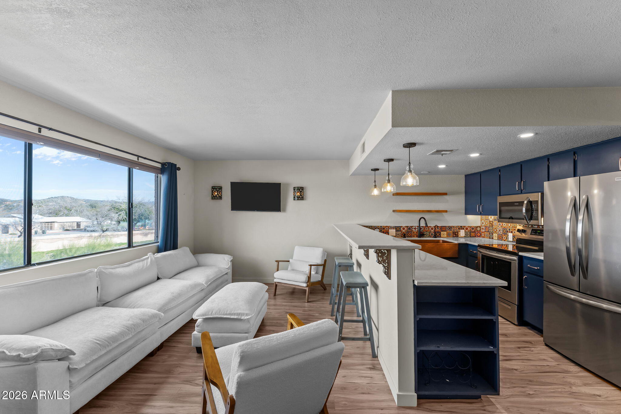 Located just a short walk to historic downtown Wickenburg, this condo puts you right in the heart of it all--steps from local dining, shopping, the grocery store, and the downtown roping arena. For team ropers and winter visitors, you're also just minutes from Rancho Rio and Roper Nation, making this an ideal seasonal home base.
Step inside to a condo that actually stands out. Thoughtfully updated, it blends modern finishes with bold southwestern character--featuring rich navy cabinetry, quartz countertops, striking artisan tile, and statement copper sinks that give the kitchen and bath a custom, designer feel. Open shelving, updated lighting, and clean lines create a space that lives larger than expected. The bathroom has been tastefully remodeled with a walk-in tiled shower and pebble flooring, while the open-concept living area captures natural light and showcases views of the surrounding desert landscape.
Enjoy peaceful mornings and Arizona sunsets from your private balcony overlooking open space--offering both privacy and a true sense of place.
Whether you're looking for a lock-and-leave winter escape, investment opportunity, or full-time residence, this one delivers style, location, and value.