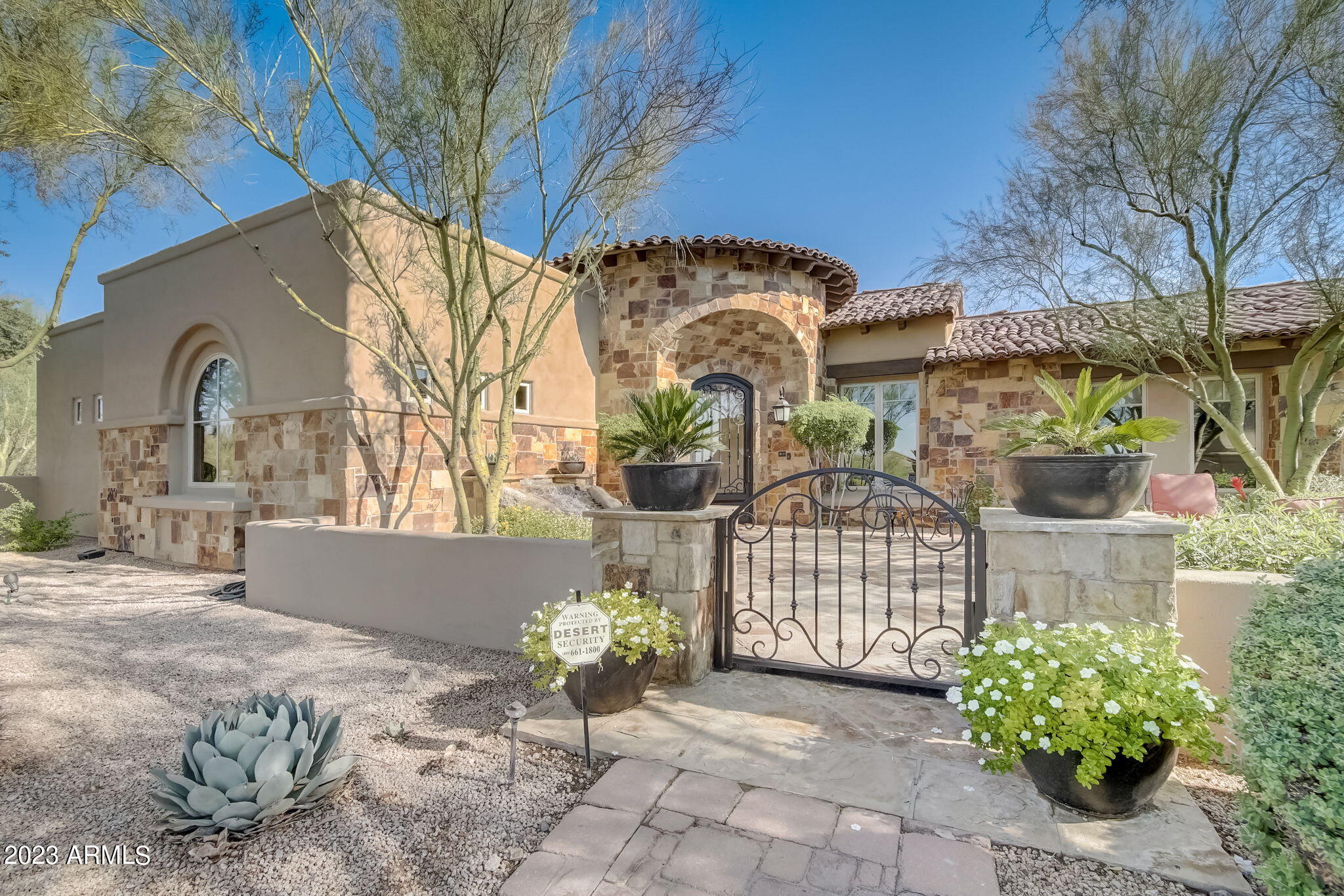 Experience the beauty of unobstructed Pinnacle Peak and Troon Mountain views surrounding this Geoffrey Edmunds custom home with separate guest house situated on 1.6 acres in gated Pinnacle Peak Place in North Scottsdale.  A true turn-key home with all furniture included (at list price of $3.2M), this luxurious home is the epitome of Arizona living offering the optimal blend of breathtaking views, exquisite finishes and a private homesite of perfectly manicured vegetation enveloping large grassy areas.  A spacious gated front courtyard entrance with fireplace and trickling water feature welcomes your approach and sets the stage for unparalleled attention to detail throughout the single level open concept design.  Centered around intimate spaces, the warm and inviting residence is a masterpiece of craftsmanship and design from the chef's kitchen offering double islands, an expansive pantry and premium Viking appliances to wood beam ceilings to Versailles stone floors meticulously placed.  Designed for entertaining and large family gatherings, the kitchen offers 3 ovens, 2 dishwashers and a 6-burner gas range, with an oversized stone island and bar with seating.  The main house includes a flex room, office, wet bar with wine tower and 3 ensuite bedrooms including a private primary suite complete with dual walk-in closets, bountiful natural light gracefully adorned with new electronic window coverings in both the bedroom and bath, and oversized sliding doors opening to a private patio.  A detached guest house is perfect for guests or multi-generational families offering a private sitting room, three-sided stone fireplace and kitchenette.  Expansive electric sliding doors seamlessly integrate the indoors with the resort backyard, opening to a stone surround pool and spa, accentuated by natural boulders, custom waterfall, firepit and endless mountain views.  Truly designed with every need in mind, the property boasts a 4-car garage with storage as well as a large motor court and generous parking for guests.  A luxurious haven for entertaining or simply relaxing, this incredible home offers the best of Arizona.