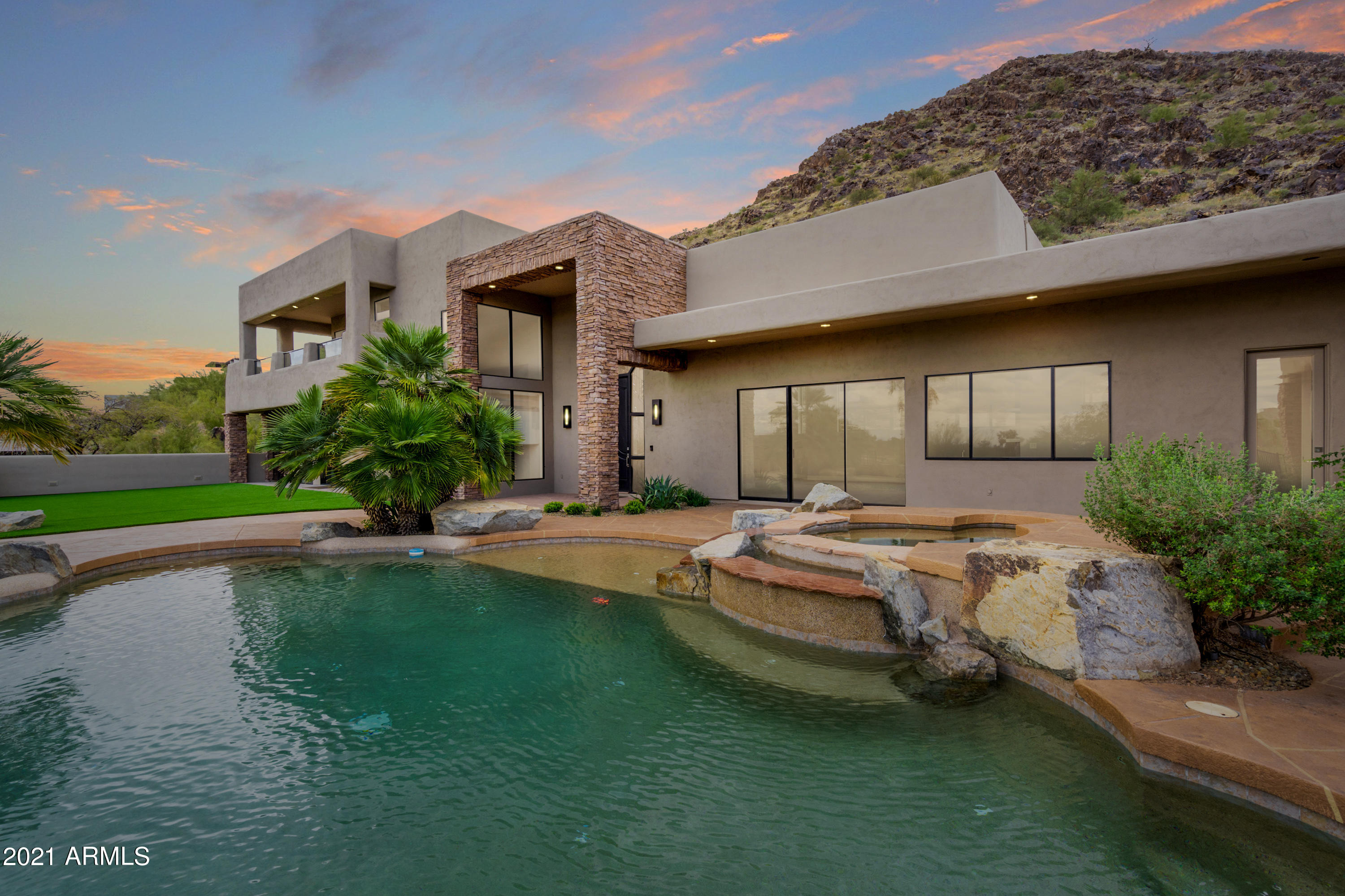 72 Hour Home Sale! Sweeping across over an acre on the NW tip of Mummy Mountain this newly renovated ultra-modern compound  offers truly spectacular 360 degrees views.  Clean lines mingle with unique design features like the focal fireplace wall with ''fins''  that change color & double as shelves.
Well thought out details abound throughout the three-story interior, which seamlessly expands to accommodate a myriad of living needs. Enjoy the  most amazing view from your master sitting area  or private deck.   Truly the epitome of modern desert living !
Features: 24 x 48 large porcelain tiles bring a sense of modern uniformity, ; built in wall wine storage custom-designed wet bars; Thermador kitchen; elevator; wraparound balcony; outdoor turf play area; modern fans and lighting, retractable doors