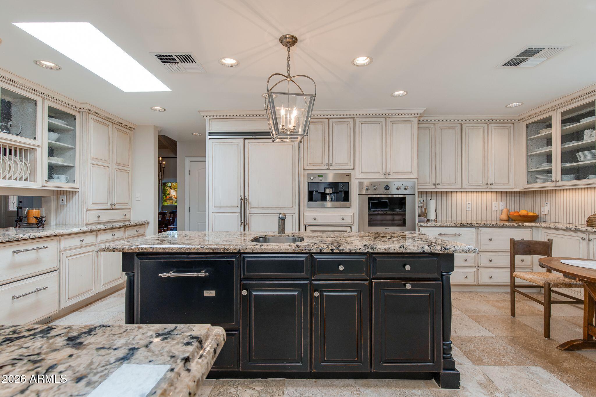 Located in the highly desired and guard-gated Biltmore Greens neighborhood. This French inspired residence features custom details throughout. Enjoy soaring vaulted wood-beamed ceilings, elegant formal living and dining spaces, and abundant natural light. The spacious island kitchen features a Viking refrigerator, double ovens, beverage drawers, wine refrigerator, warming drawer, and exceptional storage. The kitchen seamlessly opens to the family room, creating the perfect gathering space. The primary suite offers a luxurious bath with dual vanities, oversized shower, and a flexible office or exercise room with private patio access. The backyard is thoughtfully designed with a Napa-inspired feel while remaining low maintenance. Just blocks from the best shopping and dining Phoenix has