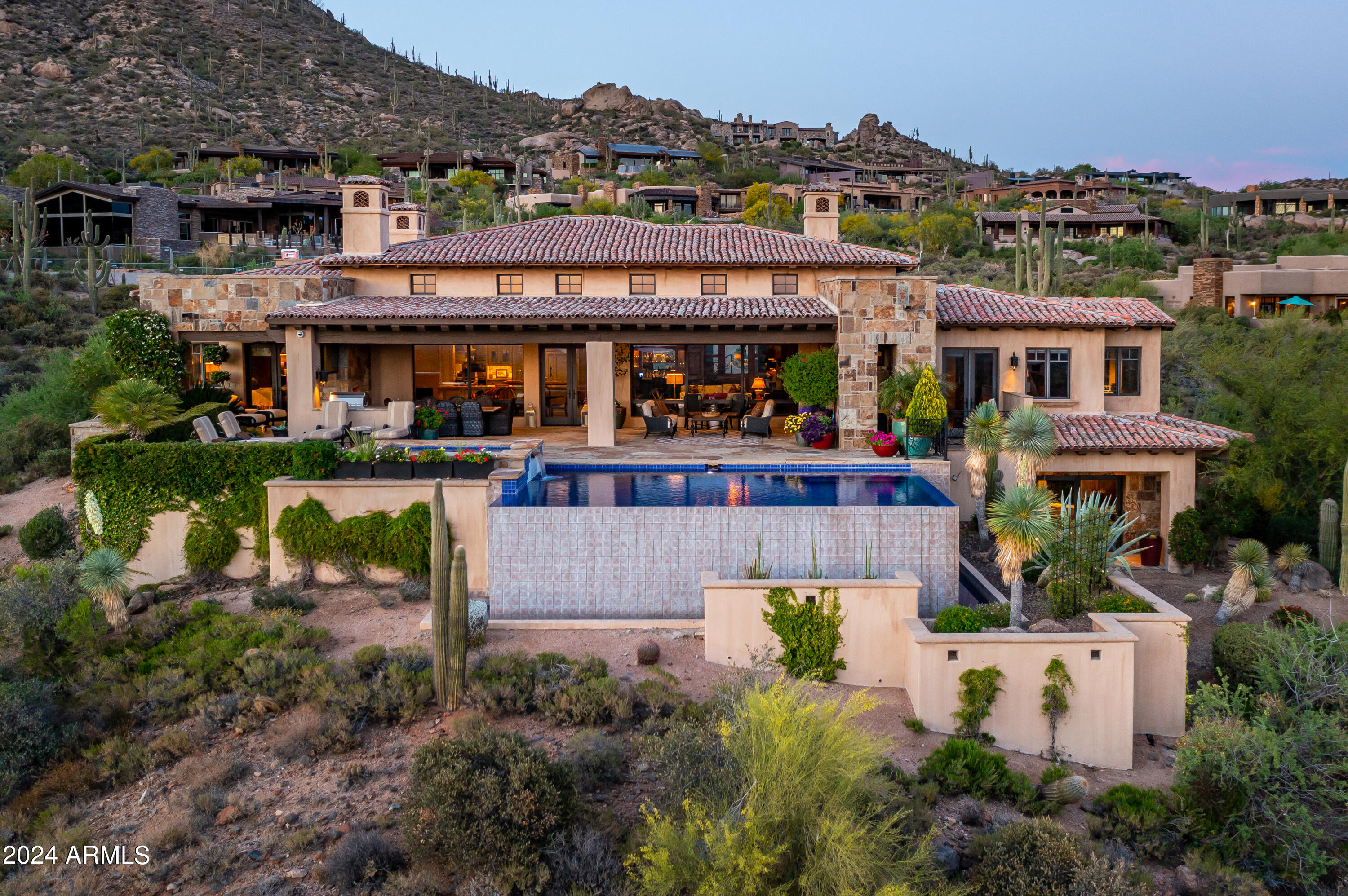 Stunning Hillside Estate with Golf membership available! Commanding views overlooking Desert Mountain,  Valley, mountain, sunset and city light vistas and beyond. Thoroughly comfortable yet elegant mountain style home featuring impressive wood beams, artisan crafted stone, wood moldings, doors and cabinetry throughout. Five Bedrooms in all including detached 2-room guest house. Entertaining sit-up bar opens to living, chef's kitchen morning room. Impressive primary BR wing with stunning bath, private view patio and hearth. Fully paneled office/library/den with private inner office. Never miss a game  ...AV system with 3 display TV's in both Great Room and Library! Extensive sun and shade patio for year-round living. Impeccable and timeless! Four-car garage. Furniture is available.