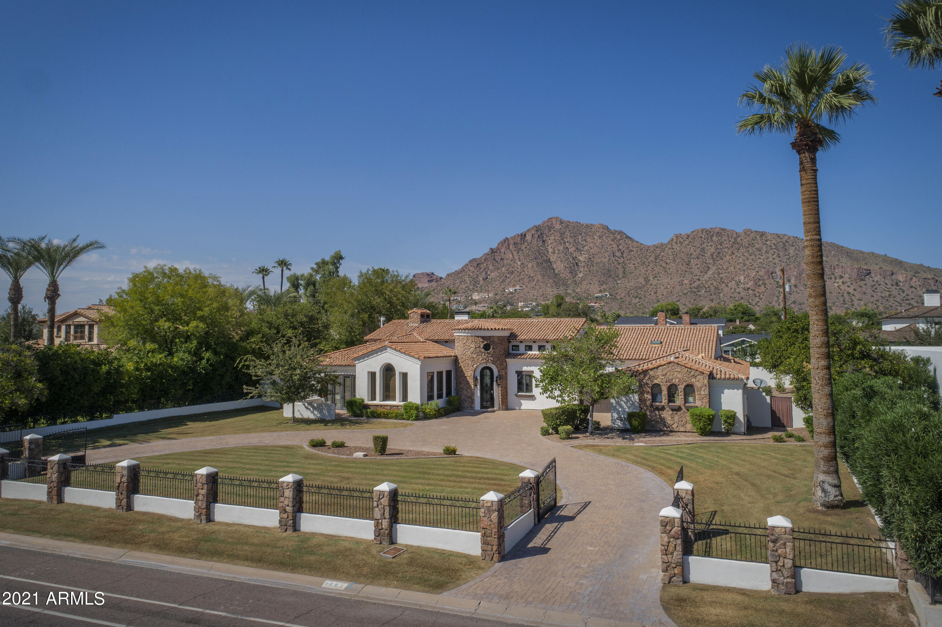 Welcome to this privately gated estate. Arcadia living with amazing Camelback mountain views, tree lined streets and this beautiful home on a little over 1/2 acre. Open concept family room and kitchen is warm and inviting with vaulted/beamed ceilings and a stone fireplace. Dinner is a delight to prepare in a beautiful kitchen with Wolf gas range, breakfast bar with built in seating and walk-in pantry. There is room for everyone with 5 bedrooms/5 baths and an additional media room. Backyard is an entertainers dream complete with a putting green, built-in bbq and a play pool with a water feature.