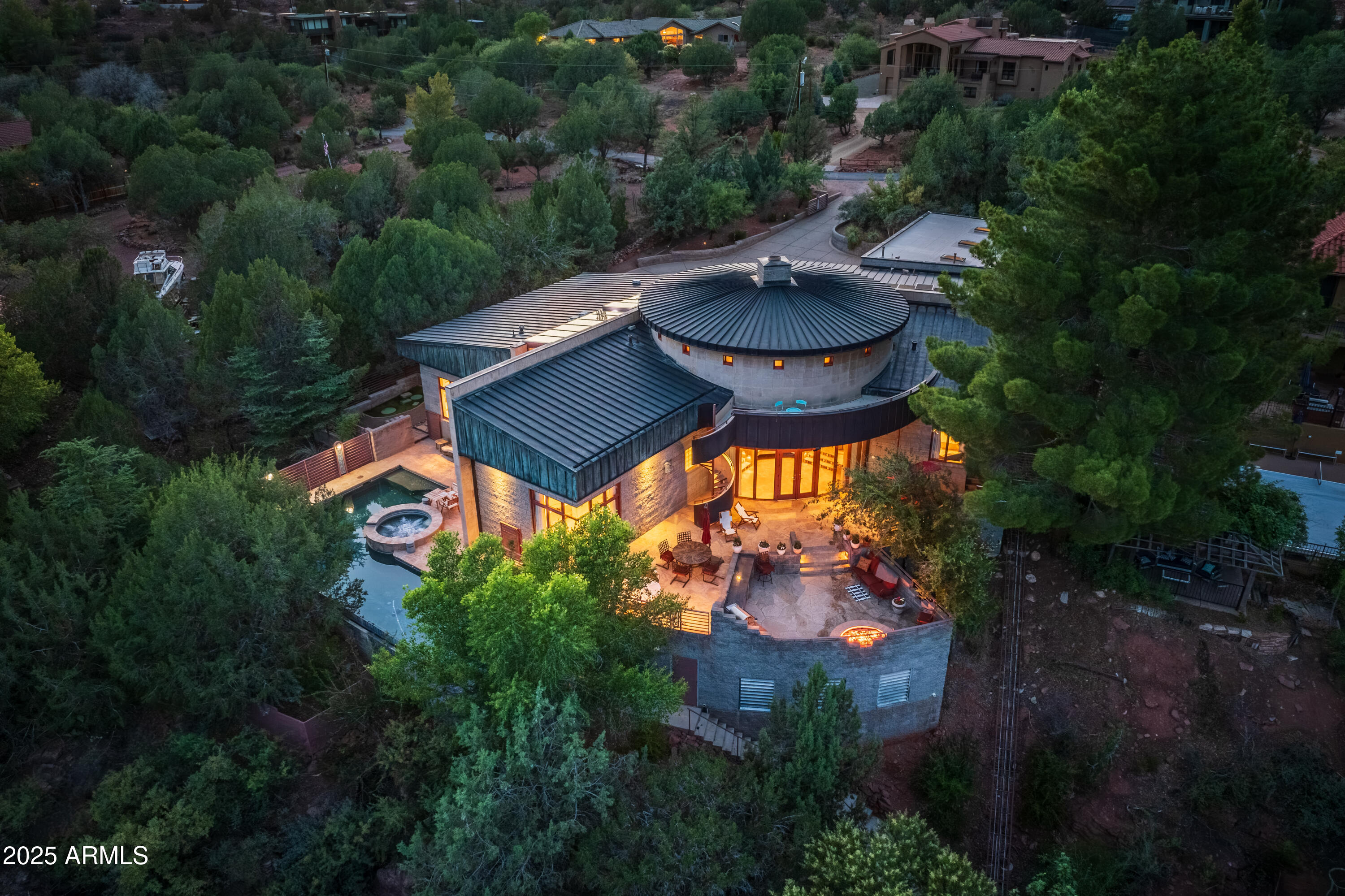 Phil Morris built this custom estate home which overlooks and runs along Oak Creek! From its' backyard decks and patios and upper view deck you will look down on your ''own private expanse of Oak Creek'' complete with negative edge pool, built-in spa, four-person tram down to the babbling creek below, next to a cascading red rock cliff waterfall! Located just .05 mi. from Red Rock State Park, arrive and enter through 80 East Wings' private gates to notice a remarkable feat of architecture, a circular copper roof and three matching copper garage doors. When you enter The Santa Cruz Home you will notice that no expense was spared in building materials. Tucked amidst lush trees and shrubs, it's built on one level semi-circle. Interior reveals towering octagon cathedral wood ceilings and custom lighting features that illuminate a unique circular ceiling for an amazing site to behold every evening! An open living area is well suited for entertaining friends and family with a three- sided gas fireplace for ambiance, multi-seating options and room for gaming and family kickback time. Attention to detail custom finishings throughout include lighted art niches, French doors, wood and copper trim, Pietra Italian marble floors and counters and fiddle-back maple cabinetry. This home provides four ample sized bedrooms (2 master suites, 3 total En-Suite), a full office & three baths. The split floor plan has dual primary en-suite bedrooms with spacious walk-in closets and access to the outdoor patios. The largest primary suite has a luxurious whirlpool bath, double sinks, private commode, lighted make-up area, and walk-in closet. Exit the primary suite to a shaded artificial turf area with fenced dog run and gated access to your private 4-person tram whisking guests down to the river below. The second primary suite has real princess charm with sitting area, stately wall to ceiling gas fireplace, full en-suite bath and private access to the serene pool/patio area. The third bedroom shares a common bath via a short hallway to the fourth bedroom, currently a beautiful yoga/Pilates/cardio barre exercise room with floor to ceiling windows looking out over the negative edge pool and spa deck. The private office looks out to the front drive and entrance with custom bookshelves, TV area and a hidden vault. The expansive patio above the river has an outdoor built-in BBQ with gas fire pit, ample room for your hosted gatherings, along with total privacy and lots of sunshine. A spiral staircase takes you to the upper deck platform with 280-degree views including Cathedral Rock to the East and ethereal star gazing all year round. The negative edge pool and built-in spa provide utter luxury while sunning, splashing with children or choose to meditate with sounds of running water below. Outfitted with Franke faucets and sinks, Kohler whirlpool bath, modern Franklin brass hardware, all custom doors throughout, Lenox dual zone HVAC Systems, and whole house Bose sound system. The gourmet kitchen is perfect for catering your happy hours with Subzero refrigerator/freezer, Viking 8 Burner stove with dual ovens, 2 Marvel wine coolers, Bosch dishwasher, large butcher block with stainless double sink, Italian marble counters and custom marble kitchen table with cushioned seating. Additionally, the oversized 3-car garage has 3 skylights, 3 parking bays and a Tesla charging station.
Ready to experience the summer of a lifetime? With approximately 4100 sq. ft. under one spectacular roof, perched on top of a red rock cliff face...this might be your ticket to paradise. The photo gallery showcases it all!
The home is in the Cup of Gold Water Assoc. which requires an annual assessment fee of $1,300 per year and a one time $5000 transfer of ownership fee.