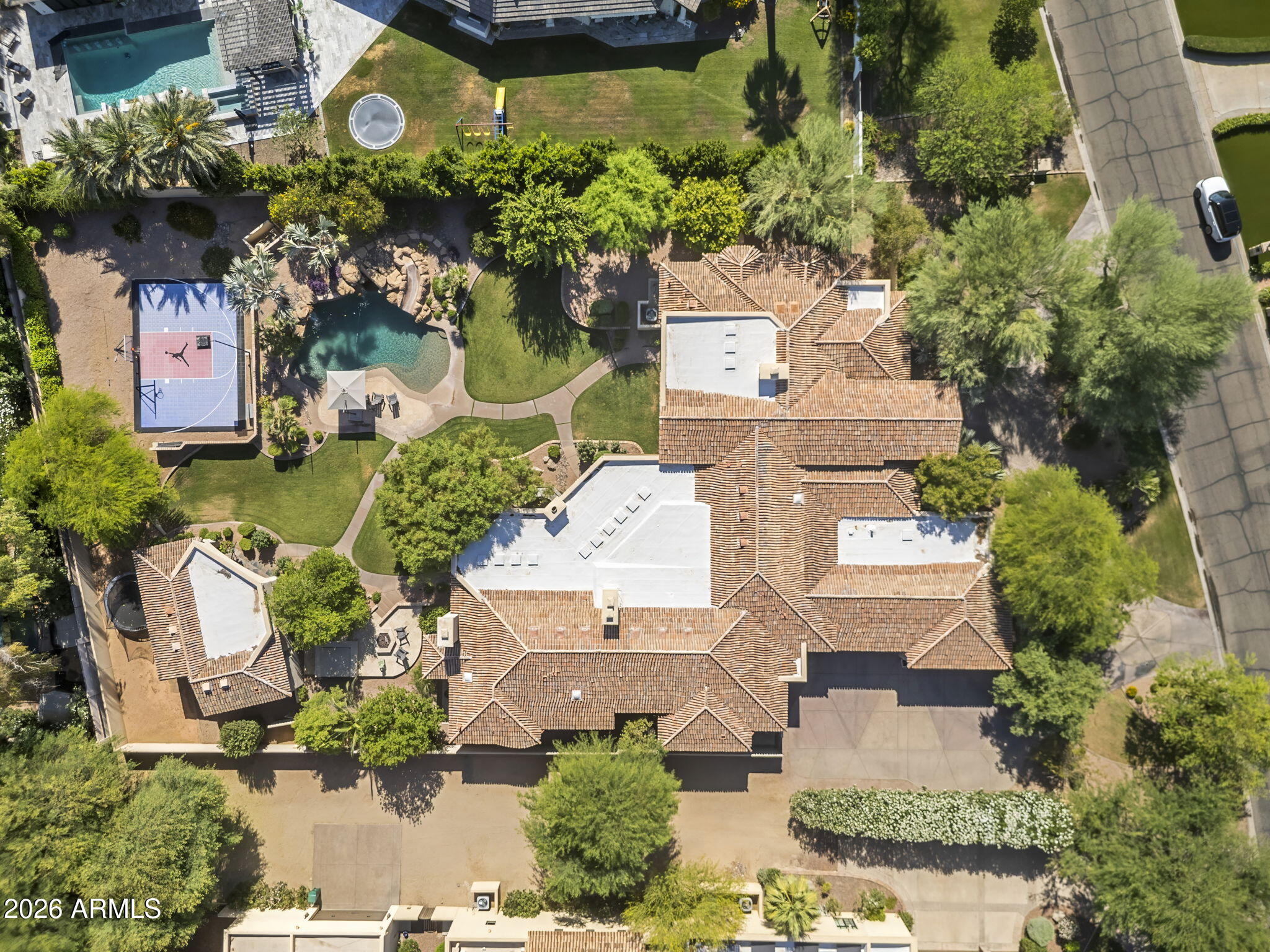 Set on just over an acre in the coveted 3 C's school district near Camelback Country Club, this exceptional estate captures stunning views of Mummy Mountain and defines peaceful luxury living. Tucked behind a large, welcoming front yard that creates a true sense of privacy, the home blends timeless elegance with thoughtfully designed spaces for both everyday living and unforgettable entertaining. The thoughtfully designed split floorplan offers four total guest suites, all featuring en-suite bathrooms and walk-in closets. Three of the guest suites are anchored around a central flex space perfect for a media room, study area, playroom, or additional lounge, while the fourth guest suite is privately positioned just before entering the primary wing of the home. The luxurious primary retreat offers dual closets, split vanities, a soaking tub, steam shower, and a private seating area with fireplace, creating a true spa-like escape.
At the heart of the home is an incredible true chef's kitchen complete with an eat-in dining area, dedicated kitchen office, Butler's pantry, walk-in pantry, two dishwashers, and seamless flow into the fully equipped walk-behind bar and expansive great room. A dramatic wall of glass opens to massive covered patios, creating the ultimate indoor-outdoor lifestyle.
The resort-style backyard is truly a showpiece, overlooking a sea of lush grass and offering every amenity imaginable -- including a custom pool with waterfall and waterslide, separate heated spa, firepit, outdoor fireplace, and sport court. Whether hosting large gatherings or enjoying a quiet evening at home, the setting is the perfect balance of luxury and tranquility.
Adding to the home's impressive functionality is a 1,200 SQFT basement/game room with attached exercise room and additional storage, along with a cleverly hidden temperature-controlled underground wine cellar. The detached 600 SQFT guest casita offers ideal accommodations with its own living room, kitchen, en suite bedroom, and walk-in closet. Additional thoughtful touches include a secondary washer and dryer located within one of the primary suite closets for added convenience.
A rare opportunity to own a private retreat in one of Paradise Valley's most desirable locations.