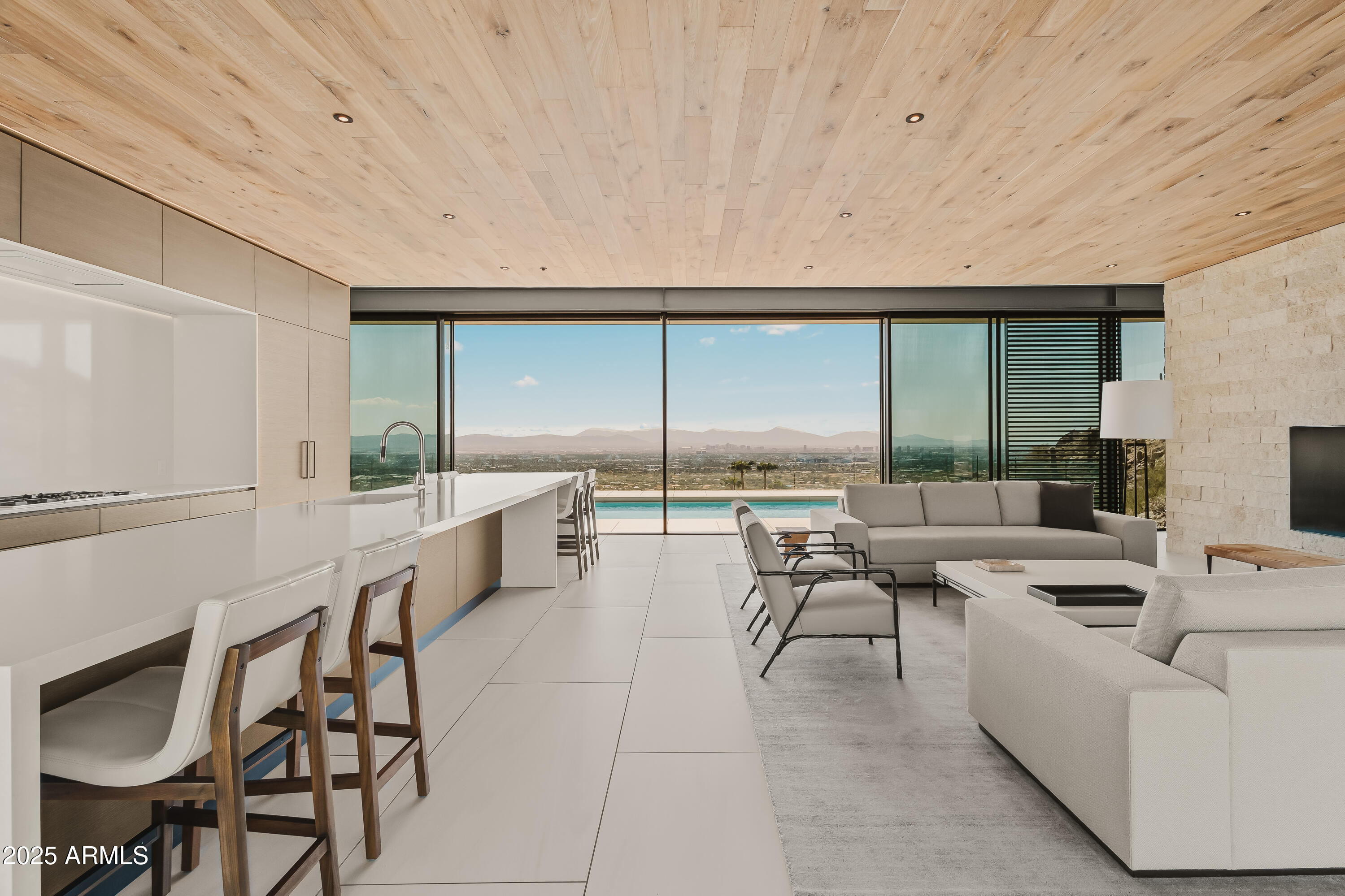 Commanding a premier 3.45-acre mountainside site in Paradise Valley, this modern estate by renowned builder The Construction Zone is a rare offering for those who expect perfection. Crafted from steel, glass, and stone, it stands as an architectural showpiece of breathtaking scale and precision. A dramatic, light-filled entry opens to soaring volumes and curated finishes, while walls of glass frame panoramic views of sunsets, city lights, and mountain silhouettes. Retractable walls create seamless indoor/outdoor living with elevated terraces, refined lounges, and a striking rooftop pool for sophisticated entertaining. Inside, luxury unfolds through expansive Neolith flooring, warm oak-planked ceilings, precision steel detailing, and custom millwork. The primary suite features dual illuminated dressing rooms and two resort-level spa baths, including a sculptural soaking tub and an indoor/outdoor shower with starlit views. A glass-clad office pavilion offers 360-degree vistas, a lounge, custom fireplace, and steel-clad bar. Additional amenities include a Dolby Atmos theater, fully equipped fitness suite, guest quarters, secondary laundry, and a conditioned four-car garage with adjoining flex space. Fully automated with Crestron and served by an elevator, this private estate defines effortless luxury and architectural excellence.