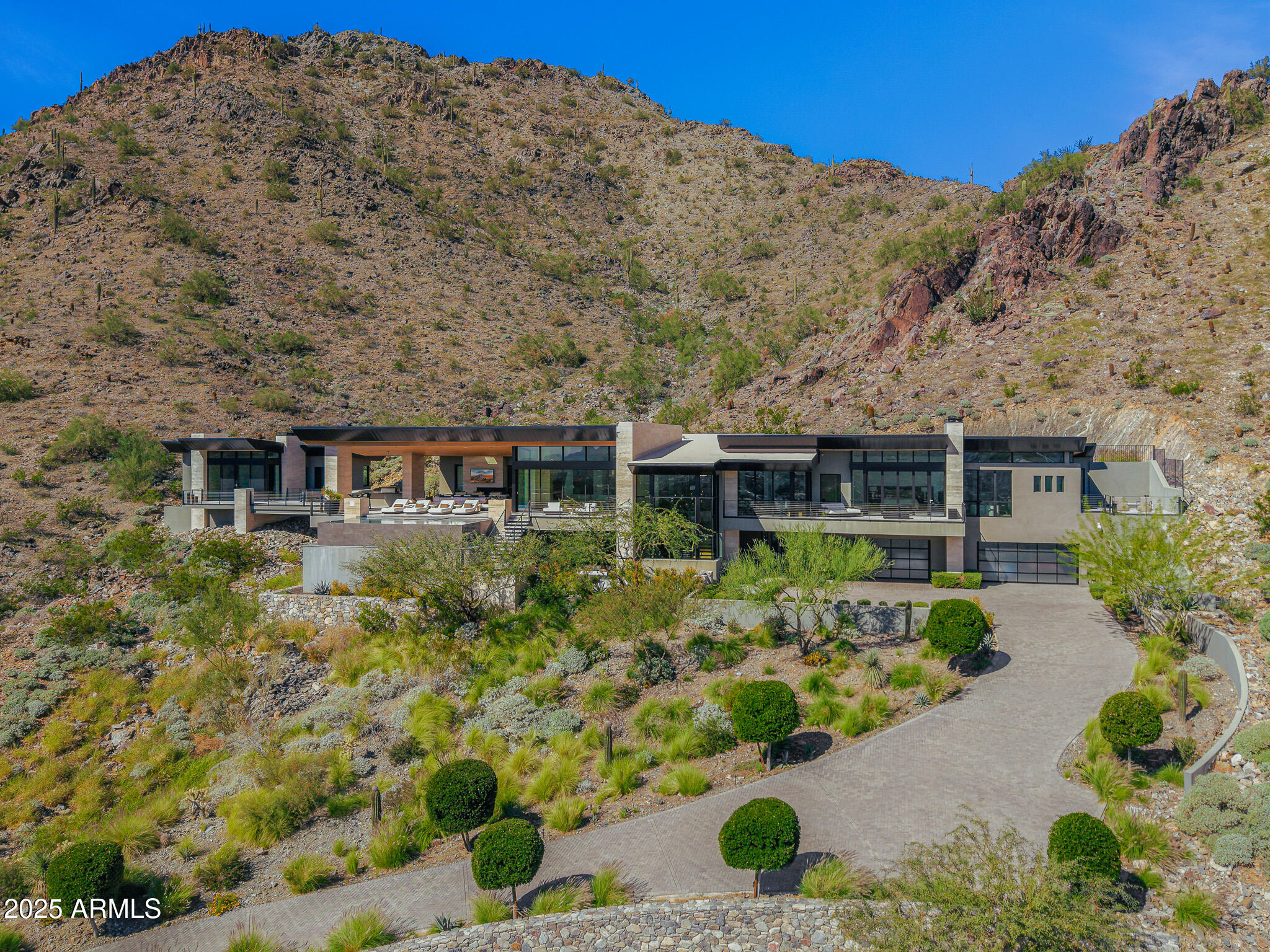Positioned on a serene hillside Paradise Reserve, this modern masterpiece showcases sleek architecture and sweeping Paradise Valley views that define luxury desert living. Designed with warm contemporary architecture, the home blends clean lines, natural stone, and rich wood elements to create a sophisticated yet inviting retreat. A dramatic staircase sets the tone upon entry, leading to expansive living spaces framed by the panoramic sliding glass doors  that open to a large covered patio, fireplaces, and an infinity-edge pool that appears to flow seamlessly into the desert horizon. The primary suite commands breathtaking views across the entire valley and features a drop-down screen & projection system, a spa-like bathroom, a massive shared walk-in closet, & a private outdoor jacuzzi... with an adjacent wellness area for ultimate relaxation. Two additional guest suites each offer private patios, while a home office provides the perfect blend of comfort and productivity. The detached guest house rivals a full residence of its own, complete with a kitchen, living area, bedroom, and bathroomideal for extended guests or multi-generational living. Every detail reflects thoughtful design and craftsmanshipwhere natural textures meet contemporary elegance, and indoor-outdoor living defines the Paradise Valley lifestyle.