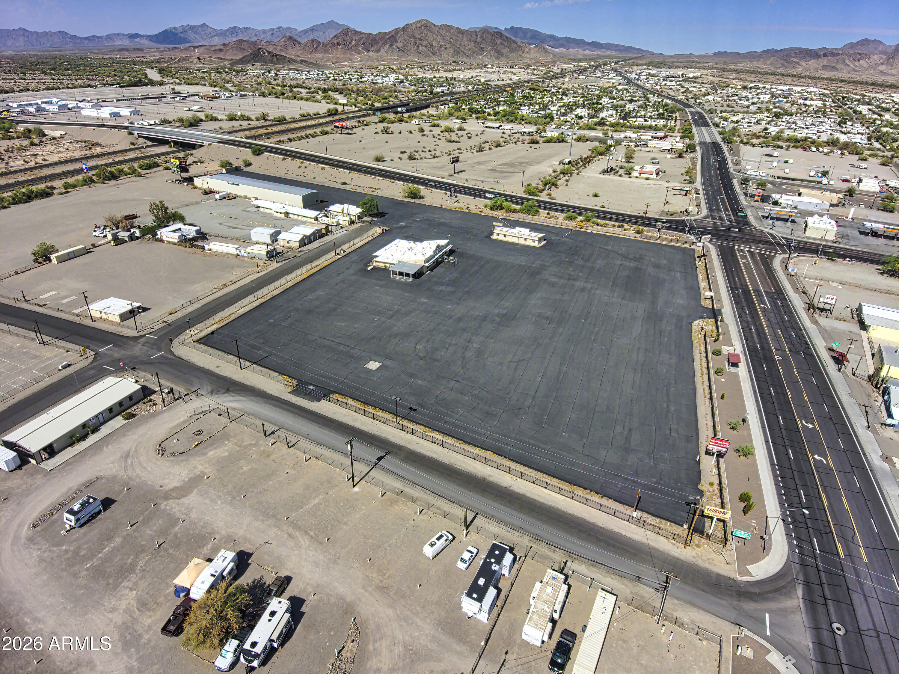 Improved 8.833 Acres at one-of-the best locations in Quartzsite: located on Highway 95, Main St, and Interstate 10. There are 4 buildings on the property totaling +-19,650 sqft under roof: 14' High Metal Building w/ 10 Bays, a Former Full-Service Restaurant/Bar (Silver Buckle), an Office Building and a Storage Shed. It is newly Paved (2021), fenced, gated and on APS Electric, Town Water/Sewer. There are Multiple Billboards Generating Revenue. Ideal for a Truck Terminal, Storage/Distribution, the Sale/Lease of Side-by-Sides, Campers, Slide-Ins, Pop-Tent Trailers, ATVs, Cargo Trailers, Motorcycles, Scooters, Personal Watercrafts, Utility Vehicles, etc. Use for RV Sales shall be Prohibited by Seller via Deed Restriction. (6) Parcels Contiguous.