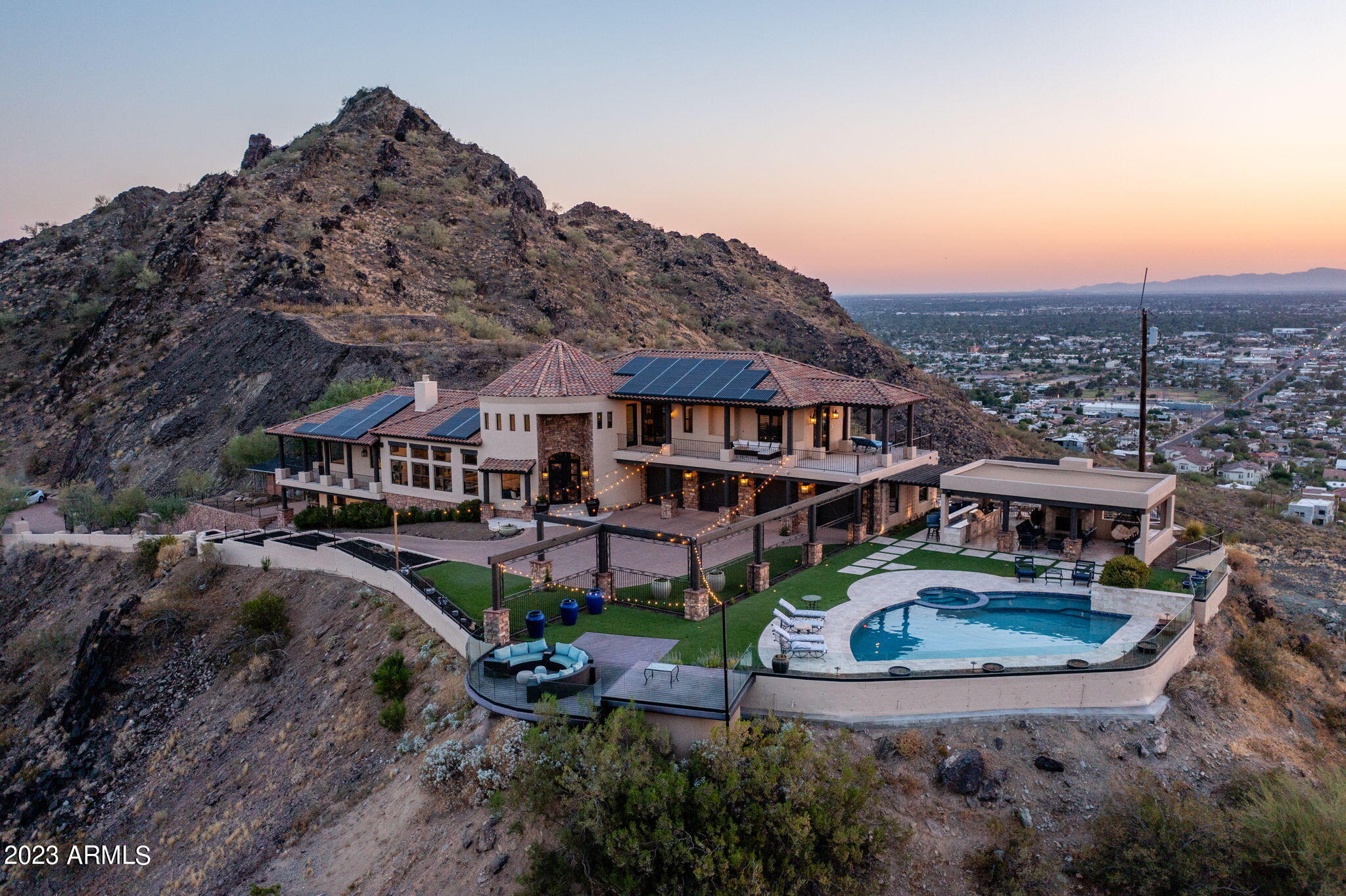 This stunning mountainside estate boasts jaw dropping 360 degree views that are unrivaled by any other property in the city. Situated on nearly 3.7 acres on the edge of the Phoenix Mountain Preserve, the city and mountain views are everchanging and include Dreamy Draw, Piestewa Peak, Lookout Mountain, North Mountain Park, Downtown Phoenix, Phoenix Sky Harbor, Chase Field, and all the way to the State Farm Stadium. As one of the highest elevated homes in the Valley, the seclusion and privacy of this property all while being centrally located in Phoenix is extremely rare. Every room of the home takes advantage of the mesmerizing mountain views. The living area has 12 foot ceilings, is filled with natural light, has hardwood floors, and a floor to ceiling natural stone fireplace. The chef's kitchen features knotty alder cabinets, quartz counters, marble backsplash, a large island, and top of the line appliances with a Wolf Range, Wolf double ovens, Subzero refrigerator and freezer, Cove dishwasher, Viking built-in microwave, a commercial ice maker, and a multi-filtered Kinetico water system. The primary suite has city and mountain views, a wrap around private balcony, two walk-in closets, blackout motorized shades, and hardwood flooring. The primary bathroom has a soaking tub with a chandelier, dual sinks, and walk in shower. Both guest bedrooms upstairs are en suites, have huge walk-in closets, hardwood flooring, plantation shutters, and access to a 900 square foot balcony. The bottom level has two additional bedrooms, laundry, storage, and another private patio. The driveway is over 7,500 square feet of paver stone with multiple parking areas, and there is a 4 car garage with an EV charging station, extra storage cabinets, and a central vac system. The outdoor living is an incredible space that has a kitchen with granite counters, stainless grill, bread warmers, and sink. There are multiple fireplaces, travertine flooring, tongue and groove natural wood ceiling, Sonos speaker system, misters for those hot afternoons, synthetic grass, and a glass surround wall to further take in the never ending views. The PebbleTec pool has a waterfall feature, new Pentair pump, spa, and is fully heated with a new Pentair heater. All 91 of the Tesla solar panels are owned outright with no balance and offer incredible electric bill savings that often result in a future credit.