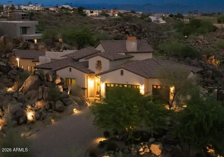 Custom head-to-toe luxury masterpiece on a 1.29-acre elevated corner lot with unobstructed Red Mountain views. The great room stuns with 20ft wood-planked ceilings, massive rustic beams, and a Cantera stone fireplace. A hand-laid brick Boveda ceiling defines the gourmet kitchen with custom distressed cabinets and premium granite. Telescoping glass pocket walls dissolve outdoors to a resort patio, negative-edge infinity pool with swim-up bar, fire feature, and outdoor kitchen gazebo. The primary suite features a butt-glass picture window framing ancient natural boulders right from the jetted spa tub. Additional guest bedrooms double as executive offices framing either dramatic boulder outcroppings or sweeping mountain vistas. Absolute custom perfection. The estate's structural engineering begins at its foundation, which was engineered and constructed without blasting by anchoring deep, steel-reinforced structural piers directly into solid mountain bedrock for permanent geological stability. High-performance, low-emissivity (Low-E) thermal glazing is installed throughout the residence, specifically engineered to reflect intense Arizona desert heat while maximizing natural light transmission and energy efficiency. Behind the walls, advanced mechanics include a dedicated gas water core system with continuous hot water recirculation, delivering instant hot water to every fixture across the single-level floor plan with zero wait time. Climate control is managed by a high-efficiency, multi-zone dual-split HVAC system designed to handle the thermal volume of the 20-foot vaulted ceilings while maintaining precise temperature balance year-round. Water quality is maintained through a high-capacity reverse osmosis filtration system feeding directly into the kitchen tap and refrigerator ice dispenser to filter out heavy desert minerals. The home's distinct millwork features heavy structural arched timber trusses crafted from high-density, rough-sawn Douglas Fir--chosen for its superior strength-to-weight ratio--which support a 20-foot wood-planked Knotty Alder ceiling. High-grade Knotty Alder with a custom warm finish and hand-applied dark accent glazing is carried throughout the interior doors and casing package. Every interior doorway utilizes specialized "nested portal" frames (applied extension jambs), setting heavy solid-core wood doors deep within secondary structural frames to distribute weight evenly, prevent framing sag, and create rich, Old-World architectural shadow lines. In the gourmet kitchen, the central chef's island is capped with a raw, hand-chiseled "living edge" granite slab, complemented by a dedicated breakfast nook featuring panoramic three-sided glass framing intimate views of the surrounding desert terrain. The pro-style culinary suite integrates a commercial-grade high-output gas cooktop with built-in electric convection wall ovens, alongside flush-mounted refrigeration set into 24-inch custom cabinetry depths and an ultra-quiet, low-dBA dishwasher system selected to absorb sound beneath the hand-laid brick Boveda ceiling. Added benefits include; Built-In High Capacity EV Charger and Integrated Central Vacuum with dedicated hard-surface and carpet care attachments.