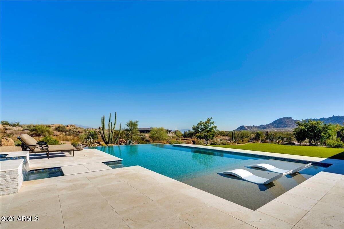 Beautiful Sonoran Desert and mountain views from this highly upgraded 4 bedroom 4.5 bath home. Located on a prime lot in the new gated community of Boulder Ranch.  The backyard is perfectly crafted for Scottsdale outdoor living.  Complete with outdoor fire pit, misting system and pool lights that can all be controlled remotely by a phone app.  The interior is appointed with Kitchen Aid and Wolf appliances, custom draperies, epoxied floor in the 3 car garage and extensive use of windows to maximize the stunning views.