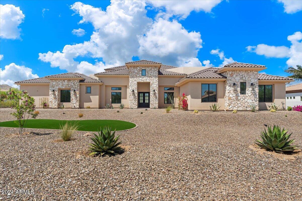 Step into the extraordinary paradise of this newly built luxury estate on over an acre and nestled within the serene, gated community of Summit at Sunrise Mountain. This unparalleled masterpiece of luxury living boasts the perfect fusion of elegance, innovation, and comfort. Revel in the sprawling meticulously crafted living space, featuring a magnificent 6,400 square foot main house with soaring 20 ft. ceilings which open up the to the well-appointed family room and kitchen accentuated by large Milgard fiberglass windows that seamlessly blend luxury with energy efficiency.  The inviting casita offers an additional 1,000 square feet of refined living quarters. The whole house has high ceilings, generously sized bedrooms and wide hallways for expansive comfort. There is exceptional foam insulation along with 5 zones of AC. Enough space has been left on the side of the Casita to build an RV garage. The main residence is a sanctuary of sophistication, featuring a grand master bedroom with fireplace, exuding tranquility, complemented by an oversized bathroom with separate shower and tub with no expense spared on the lavish decor. Attached to the bathroom is a large walk inn closet with a center island. In the East wing you will find an exclusive exercise room for wellness enthusiasts, art or yoga studio, or make it an additional 5th additional bedroom (7 bedrooms all together) the possibilities are endless. With a total of 4 additional lavish bedrooms, every member of the family is granted their own personal haven. Hosting gatherings is a breeze with the expansive great room and a gourmet eat-in kitchen that is as functional as it is luxurious, complete with Omega cabinets and top-of-the-line Wolf and Sub-Zero appliances. The West wing boasts two of the four bedrooms and a home theater replete with a Sony projector and 130 inch screen and stadium seating. The main house also contains a formal dining room and study with a set of glass French doors. A full laundry with Samsung appliances and a mud room complement the house. The 3 car garage has a finished floor with storage cabinets. In addition the house has a built in WIFI 'mesh' to eliminate any wifi dead spots and a security system with cameras. Give in to the allure of outdoor entertainment with your private oasis. As the sun sets, cozy up with the warmth of the outdoor fireplace and enjoy mountain views through the silhouette of mature Saguaros blended into a scenic landscape that will elevate the ambiance of every gathering. On over an acre this backyard retreat boasts a 17x35 foot sparkling pool accompanied by a rejuvenating Jacuzzi and built-in cleaning system for hassle-free maintenance. Share your culinary delights with the outdoor barbecue and pizza oven, perfectly paired with elegance and functionality. The covered patio, adorned with travertine pavers, sets the stage for alfresco dining and leisurely lounging, while the mesmerizing water sheet and Baja platform add an element of serenity to your outdoor escape. For those hot days a mister is installed to keep the covered patio cool. The backyard has artificial turf and a putting and chipping green to help shave strokes off your handicap. Not to be outdone, the charming casita beckons with its own allure, featuring a fully equipped kitchen, a large comfortable master bedroom, and a gracious great room, along with two baths including one conveniently accessible from the pool area. Embrace the epitome of luxury living with the stunning stonework embellishing the exterior façade, flawlessly complemented by the timeless stucco finish, creating an aesthetic masterpiece that is both striking and enduring. Experience a lifestyle beyond compare at this exclusive luxury estate. Your dream home awaits - seize this fleeting opportunity to indulge in the pinnacle of Arizona luxury living.