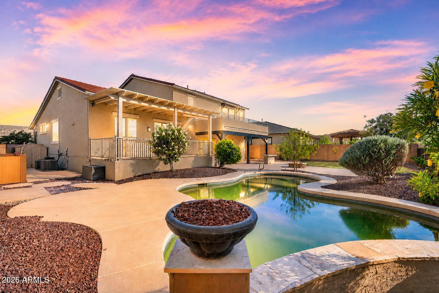 Perched among the scenic desert landscapes of Goodyear, this home blends generous living spaces, elevated views, and exceptional indoor-outdoor living. The heart of the home is a beautifully appointed kitchen with granite countertops, rich cabinetry, a center island, and seamless connection to the surrounding gathering areas, making entertaining effortless. Upstairs, a private view deck captures sweeping mountain and desert vistas, creating the perfect spot for morning coffee or Arizona sunsets. Outside, the backyard retreat features a pool, covered patio, fire pit, and multiple spaces designed for relaxing and hosting year-round. Conveniently located near parks, trails, golf, shopping, dining, and everyday conveniences.