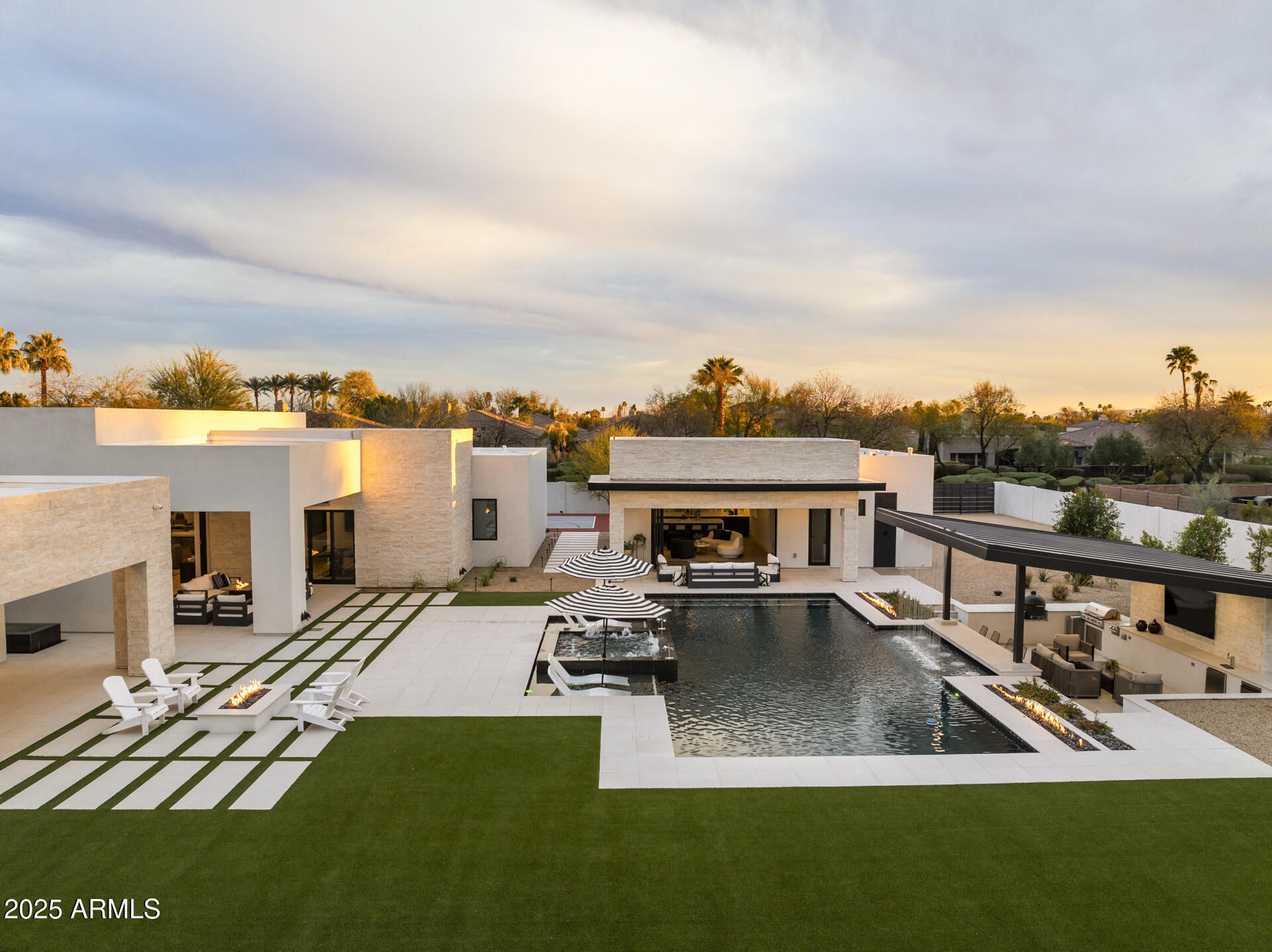 Tucked away in one of Scottsdale's most exclusive and sought-after hidden enclaves, this luxury custom estate is a rare offering for the discerning buyer that embodies the pinnacle of high-end desert living. Just under 6,000 square feet of meticulously designed interior space. Between the main house (4,853 sf) and casita (1,119 sf), this property offers 5 bedrooms, 5.5 bathrooms with an array of luxury features both inside and out; the perfect blend of elegance, functionality, and serenity for the sophisticated buyer. From the moment you arrive, this Scottsdale dream home impresses with commanding curb appeal, a beautifully landscaped front yard, and and grand entryway framed by iron doors opens into a stunning interior where soaring ceilings, wide-plank wood flooring, and custom architectural details immediately set the tone for the level of craftsmanship throughout the home. Designed with a refined yet inviting aesthetic, the expansive open floor plan was made for modern luxury living. Large picture windows and sliding pocket glass doors throughout the main living areas flood the home with natural light, while offering seamless indoor-outdoor flow; perfect for entertaining or enjoying the tranquility of the desert setting. At the heart of the home is the gourmet chef's kitchen, an entertainer's dream outfitted with top-of-the-line stainless steel appliances, a professional-grade gas range, 4 ovens, a built-in refrigerator, custom cabinetry, quartz countertops, 2 dishwashers and a spacious center island with ample seating. A walk-in pantry provides additional storage, and the adjacent wet bar formal dining area is ideal for hosting family gatherings or elegant dinner parties. Whether preparing meals or gathering with guests, this kitchen is designed for connection, convenience, and style. The great room exudes warmth and sophistication with its gas fireplace and designer lighting. The thoughtful layout creates an expansive indoor/outdoor living space perfect for entertaining large groups and family. Every space has been optimized to reflect the needs of today's luxury lifestyle. The primary suite is nothing short of a personal sanctuary. Generous in scale, tufted with velvet and metal redefining design, it features private access to the backyard and a spa-inspired en-suite bathroom with dual vanities, quartz countertops, an oversized walk-in glass shower with designer tile, a freestanding soaking tub, and a large his and her's walk-in closet with custom built-in organization. Every detail is intended to evoke a sense of calm, luxury, and privacy. Each of the additional four bedrooms is spacious and offers en-suite bathrooms and walk-in closets, making them ideal for children, guests, or multi-generational living. Thoughtfully placed throughout the home, these rooms allow for both privacy and connection. The most compelling features of this Scottsdale estate is the resort-style backyard, designed to capture the essence of indoor-outdoor Arizona living. Step through disappearing sliding doors onto the numerous and covered patios, complete with a misting system, ceiling fans, and multiple lounge areas. The centerpiece is a custom heated black pool and elevated spa, swim up bar and rain stick flanked by lush, mature landscaping with zero telephone wires that offers both beauty and privacy. An outdoor sunken kitchen with built-in barbecue, beer tap, and a beverage fridge allows you to enjoy alfresco dining and drinks under the stars, while the gas fire pit areas provides a cozy spot for year-round evening gatherings. Whether hosting a sunset happy hour, charity event, epic pool party or simply a relaxing day in solitude, the backyard delivers the ultimate in desert luxury. This estate is ideally located in the heart of Scottsdale, just 20 minutes from the airport and some of the most desirable destinations in the Valley! Enjoy proximity to Old Town, Talking Stick, Kierland Commons, Scottsdale Quarter and Fashion Square offering upscale shopping, five-star dining, and lifestyle experiences. For golf lovers, you are surrounded by world-renowned courses. Outdoor enthusiasts will appreciate the quick access to McDowell Sonoran Preserve, where hiking, mountain biking, and horseback riding trails abound. The home is also located near top-rated Scottsdale Unified schools, as well as premier private and charter schools, making it a top choice for families seeking both luxury and lifestyle. This home is more than a place to live; it's a statement. It represents everything that luxury buyers seek in a Scottsdale estate home: timeless architecture, thoughtful design, resort-caliber amenities, and a location that delivers access to the very best of Arizona living. Whether you are searching for a primary residence, a seasonal retreat, or an executive home for entertaining, this property offers the versatility, scale, and luxury you've been looking for. It's not just a home, it's a lifestyle investment.
*** Garage is technically 3.5 but owner can easily convert to full 4 car garage with the right offer.
