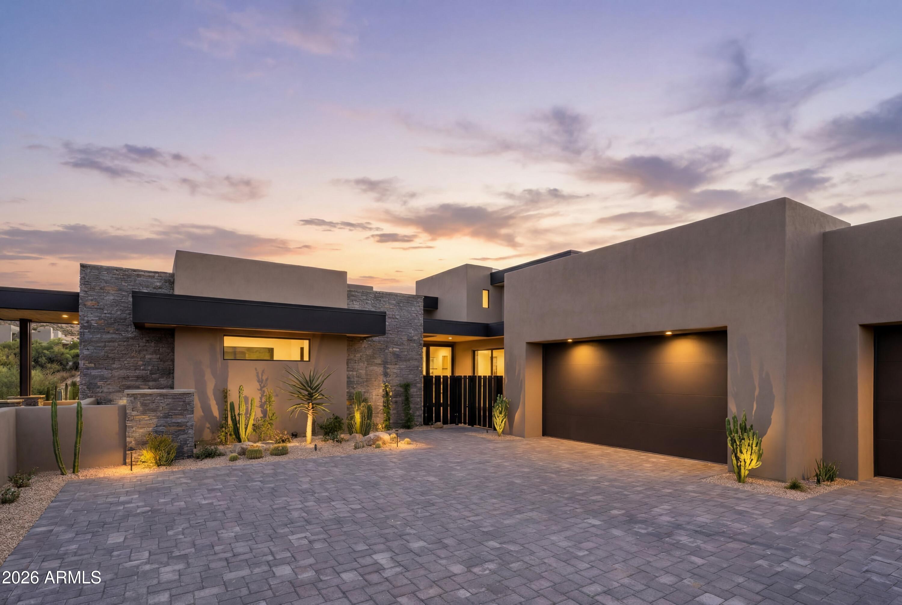 DM Golf Membership included-An extraordinary architectural vision emerges from the Sonoran landscape - designed by Beau Graffin and built by Black Stone Development. The home is sculpted by dynamic rooflines, organic stone, steel, and sweeping walls of glass that dissolve the boundary between indoors and out. From every elevation, the interplay of natural light and desert sky creates a living glow that shifts with the sun, making this home feel perpetually, breathtakingly alive. The gated courtyard entry announces itself with quiet authority -- and the illuminated interior beyond stops you in your tracks. The main-level great room is an architectural statement in its own right: soaring ceilings, a freestanding floor-to-ceiling fireplace, and a seamless wall of glass opening to the covered, heated outdoor living and dining terrace. The kitchen is a chef's dream -- a dramatic 6' × 10' island, three walls of under-lit cabinetry, and a full suite of Wolf, Cove, and Sub-Zero appliances, anchored by a generous walk-in pantry and a back kitchen with coffee station and wine refrigerator for effortless entertaining. Three distinct outdoor spaces unfold across the property. The main terrace offers covered and heated living, dining, a pool, spa, and grilling area. A second courtyard invites with a 4-hole putting green and a linear fireplace ideal for stargazing. The upper-level patio -- warmed by its own fireplace and television beneath a stacked stone wall -- completes the picture. The main level primary suite is a sanctuary: a floor-to-ceiling fireplace, a luxurious spa bath, and a designer walk-in closet curated to impress. Two additional ensuite guest bedrooms, a powder room, and a designer laundry complete the main level in style. A statement underlit staircase -- framed by magnificent windows at every turn -- ascends to the upper level, where a guest bedroom, full bath, and a den or media room offer total privacy and relaxation. At the corridor's end, a flexible studio, fitness room, or additional bedroom is wrapped on three sides by windows framing the untouched desert beyond. The color palette presents light wood plank flooring, white walls and tile accents, beiges and greys with black fixtures, hardware and details. Situated within one of Arizona's most coveted addresses, Desert Mountain offers seven championship golf courses, seven architecturally distinctive clubhouses, world-class dining, and over 20 miles of private trails bordering Tonto National Forest. This mid-mountain location balances total privacy with easy access to Scottsdale's cultural scene, upscale shopping, and Phoenix Sky Harbor International Airport. This is not simply a residence -- it is an invitation to live exceptionally, where architectural integrity meets the majesty of the Sonoran Desert. A membership is available at an extra cost.