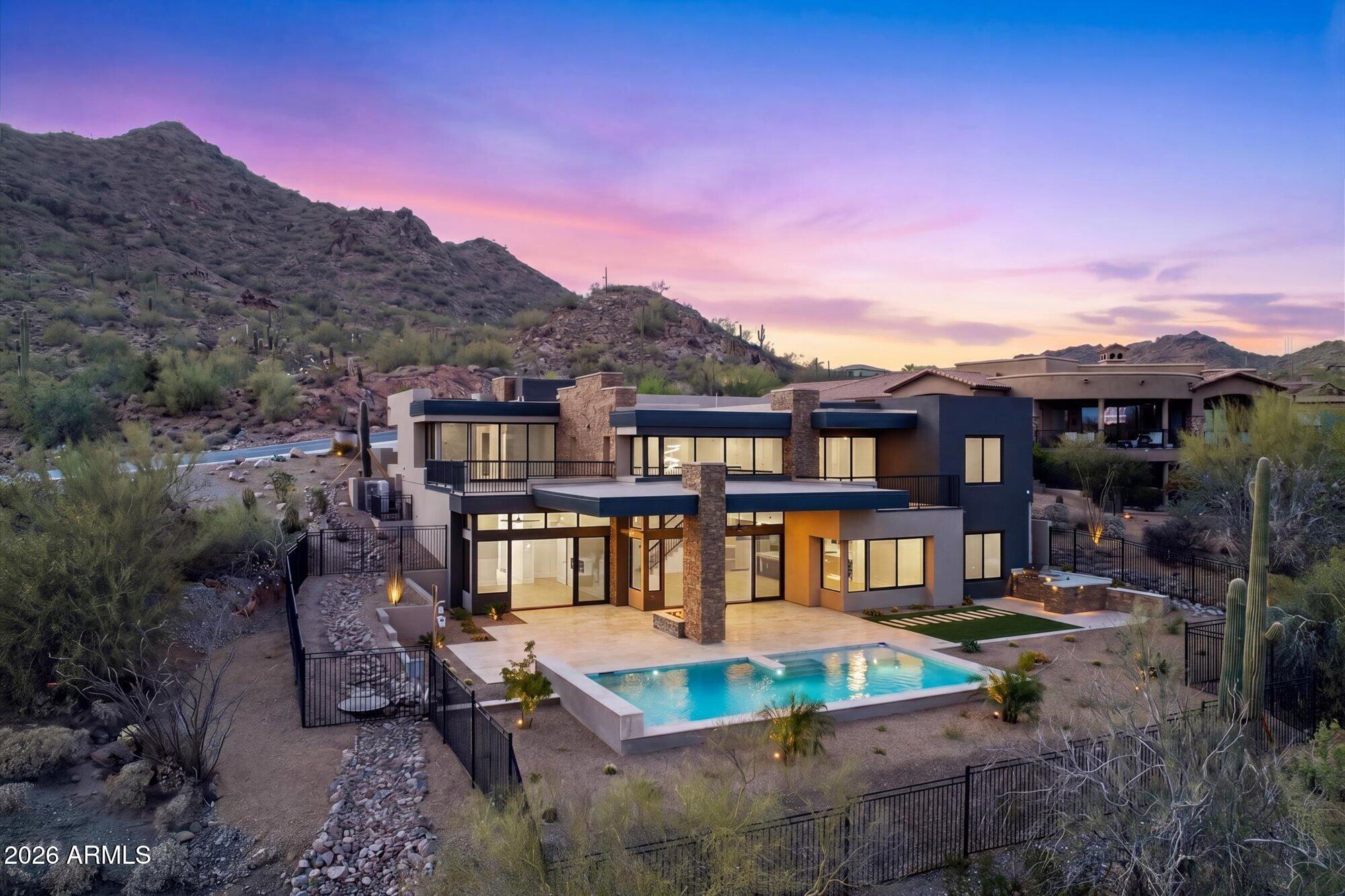 Immerse yourself in the charm of this stunning, newly finished two-story haven, crafted with precision by MSN Group, set in the lively heart of Hidden Hills with breathtaking views of surrounding mountains. Encompassing 5,866 square feet, this residence is a beautiful fusion of sophistication and practicality, featuring 6 spacious bedrooms, each with a generous walk-in closet, and 6 lavish en-suite bathrooms, along with a convenient powder room and a dedicated office. The gourmet kitchen serves as a chef's paradise, seamlessly connecting to a grand great room, complete with a stone fireplace that exudes warmth and invites gathering and relaxation. Adding to its convenience, a built-in elevator provides effortless access to both floors. The primary suite offers serene desert views, dual walk-in closets, and a luxurious bathroom with a walk-in shower and jetted tub. Other highlights include designer cabinetry, premium finishes throughout, and an oversized three-car garage. Outdoors, discover a sprawling patio, a fully-equipped outdoor kitchen and entertainment area, and a sparkling pool with cascading waterfalls. Perfectly situated in Scottsdale, this home exemplifies luxurious modern living, offering a lifestyle defined by elegance, comfort, and unparalleled sophistication.