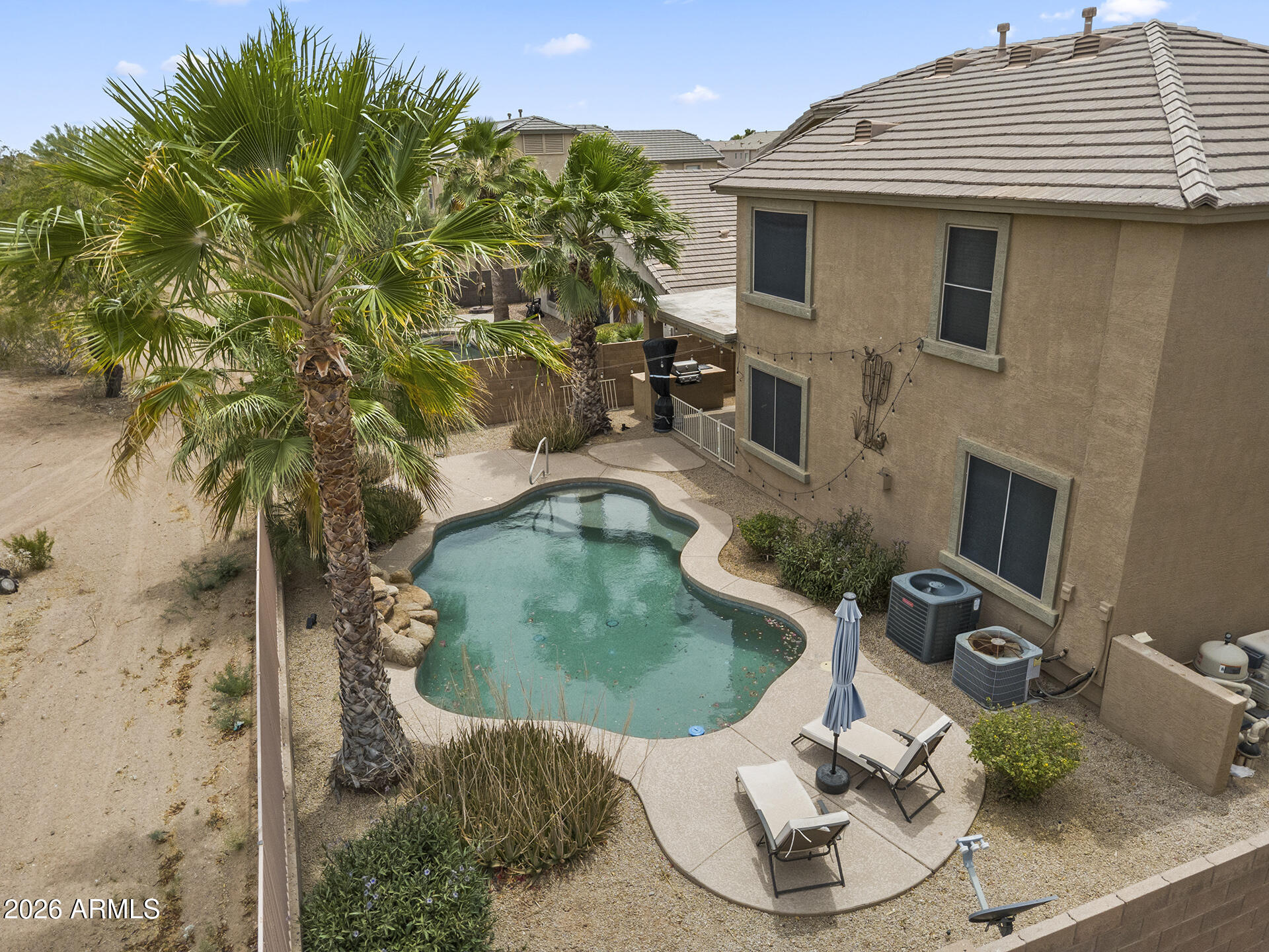 Golf Course Poolside Living! Spacious Maricopa home featuring a flexible formal living room off the entry, with a separate formal dining area through an elegant archway. The main family room impresses with soaring vaulted ceilings, statement staircase, cozy fireplace & abundant natural light, flowing into the kitchen with light oak cabinetry, granite countertops, center island, breakfast bar seating, eat-in dining area, extensive cabinetry, large windows & direct backyard access. Downstairs also includes a bedroom, full bath & separate laundry room for added convenience. Upstairs opens to a versatile loft space, while the primary suite features vaulted ceilings, abundant natural light & an ensuite with dual vanities, separate soaking tub, glass walk-in shower & oversized walk-in closet. Three additional upstairs bedrooms all include ceiling fans & share a full bath with shower/tub combo. The backyard is designed for entertaining with a sparkling pool, waterfall feature, built-in BBQ, covered patio & golf course views through wrought iron fencing. Located in a community with parks, playgrounds & ponds woven through the golf course, plus convenient access to shopping, dining & recreation.
