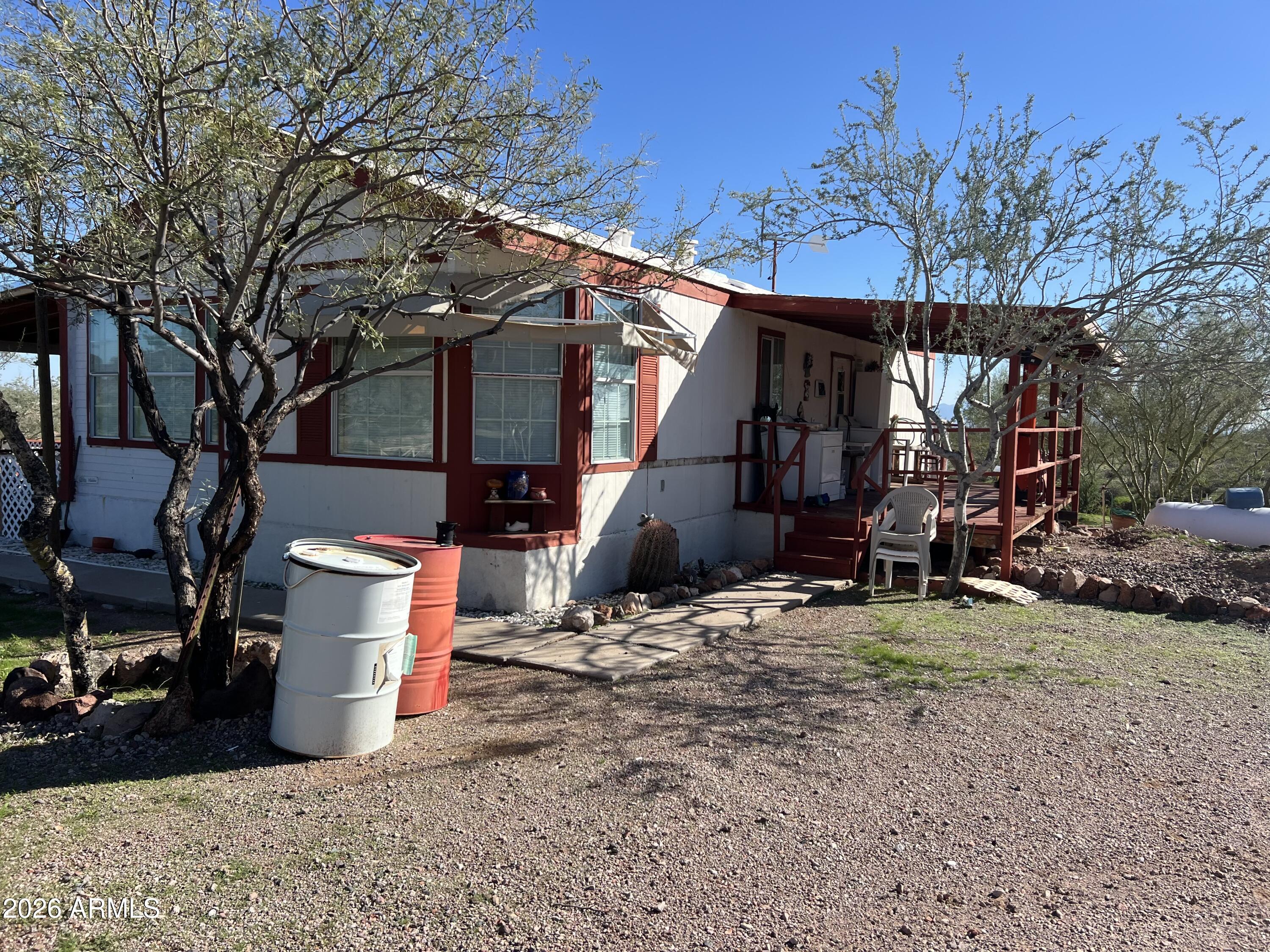 Manufactured home with 3 bedrooms and 2 baths located in Whispering Ranch in Wittmann, AZ.  This home sits on 5 acres and off grid with scenic views. Home also has a large storage container and other storage rooms. Green house that can also be turned into a chicken coup. This property has plenty of space for your horses and other animals.  Home has septic, hauled water. All you need is to add solar panels with battery to power it up.  If you want to have privacy well this is it.  FIX UP OPPORTUNITY.