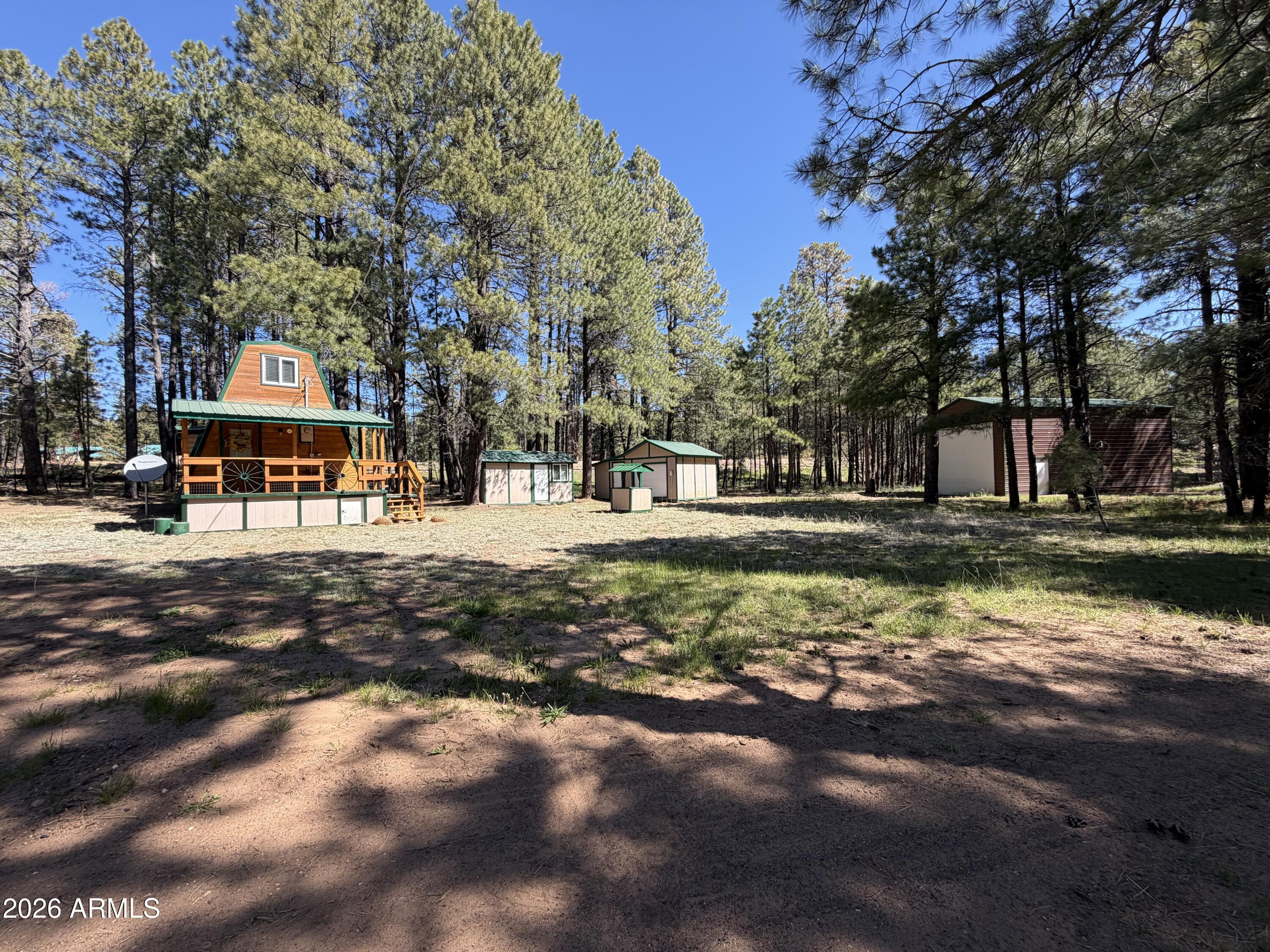 Escape to the cool pines with this inviting 2-bedroom, 1-bath A-frame cabin in Forest Lakes Estates, perfectly situated right off the main highway for easy, year-round access. Nestled on over 1.5 acres of serene, tree-lined land, this property offers the ideal balance of privacy, space, and opportunity--now enhanced with commercial zoning, making it perfect for a getaway, rental, or business venture.

Inside, you'll find a warm and welcoming cabin atmosphere with rich wood finishes throughout. The main level features the living room, bathroom, and a cozy wood-burning fireplace, creating the perfect space to gather and unwind during crisp mountain evenings. Both bedrooms are located upstairs, offering a quiet retreat after a day spent enjoying the outdoors. Best of all, the home is fully furnished, making it truly move-in ready.

Step outside and take in everything this expansive property has to offer. A seasonal creek meanders through the lot, adding a peaceful, storybook charm. There's plenty of room for entertaining, relaxing, or expanding, with ample space for RVs, boats, and recreational toys. The property also features a huge RV garage, workshop/shed, and unfinished additional living space, giving you flexibility for storage, hobbies, or future guest accommodations.

Spend your evenings gathered around the firepit under the stars, surrounded by the quiet beauty of towering ponderosa pines. Whether you're looking for a private mountain escape, an income-producing property, or a unique commercial opportunity, this one delivers.

Conveniently located under an hour to Payson, 45 minutes to Show Low, and approximately 2 hours from the Valley, this property offers both accessibility and that "getaway" feeling buyers are searching for.

There is no HOA but the subdivision does have a FLOA- Forest Lakes Owner Association with a $50 annually fee, please, see documents Tab for information