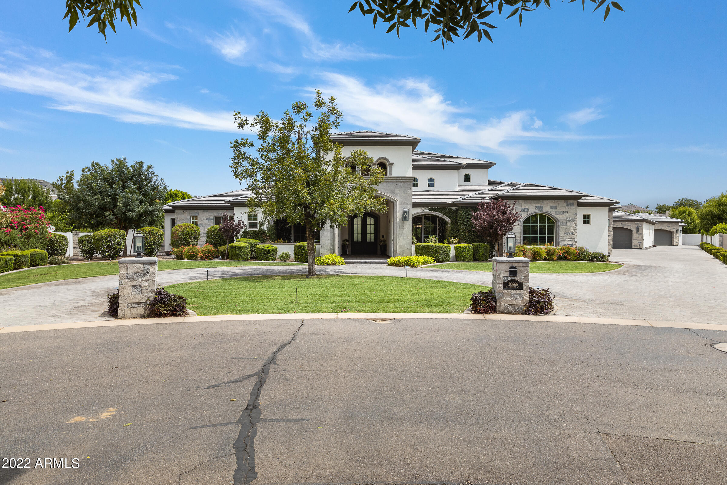 This custom home, built by E&A Custom Homes, presents a rare opportunity to live in a woodland paradise in the desert. Mature trees and landscaping, and a sprawling lawn welcome you to this modern estate, with a detached casita and a total of nine garage spaces. The main home has 4,885 livable square feet, which includes 4 bedrooms, 3 full bathrooms, a powder room, and full pool bathroom. Inside the glass and iron double door entry way, you are greeted by a large foyer that opens to both the great room and formal dining room. The gallery beyond the formal dining has a built-in bar and leads to butler's pantry with a Sonic ice maker. In the butler's pantry, look up! The coved ceiling in the butler's pantry has been tiled with sparkling tile imported from Italy. The chef's kitchen has a subzero refrigerator, tons of cabinet space, an expansive island with marble counter tops, and a walk-in pantry. The kitchen opens to the great room which has a built-in entertainment center and LED fireplace. The great room has a wall of glass sliding doors that open to the extended outdoor living space. A media/billiards room is tucked just behind that great room, which also has a wall of glass sliding doors open to the outdoor living space. The media room has custom blackout drapery and sound proof insulation on all walls and ceiling, allowing for the perfect home theater. Tucked down a hall, is a den, powder room and  3 secondary bedrooms. Two of those share a Jack & Jill bathroom, and the additional has an en-suite bathroom. The master bedroom sits in the rear of the home, off of the master foyer. The en-suite bathroom in the master bathroom has a free standing soaking tub, walk-in shower, dual vanities, and two large walk-in closets. Concealed in one closet is a hidden vault room. The main home has a five car garage and two large storage closets. The ADA compliant casita has an additional full bedroom and sitting area, kitchenette, washer and dryer, and full bathroom with walk-in closet. An additional one car garage is attached to the casita. At the very rear of the almost acre lot is a car lover's dream! Here you'll find an additional detached, three-car garage, with workshop and storage room. The backyard oasis has play pool, spa, full pool bathroom, outdoor kitchen, fire pit and yard lined with mature citrus and pecan trees. The home has a whole house sound system, with speakers throughout the interior and an outdoor system that includes two 1000 watt, in-ground subwoofers and ten outdoor speakers. Additional features include permanent holiday lighting and a professionally installed misting system on the back patio. Living at The Pecans affords a completely different experience from typical Arizona communities. Come home to canopied boulevards with wide, tree-lined medians fronted by custom homes. The community is alive with parks, playgrounds, splash pad, a putting green, and miles of walking and biking trails. And everywhere there's the splendor of the trees with their cooling shade, lush foliage and ever-changing colors. The Pecans is referred to as an Arizona surprise because a feeling of unexpected wonder is the reaction from everyone who is introduced to this extraordinary property. For the past 30 years The Pecans has been a working grove with thousands of mature pecan trees. In this enchanting environment, is a custom estate community with just 258 Queen Creek Home sites.