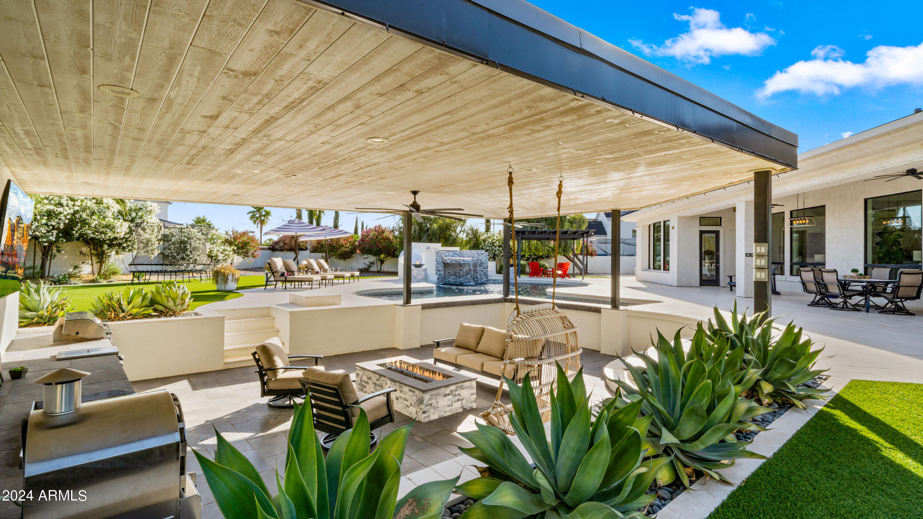 Introducing one of the Valley's premier estates, nestled behind the prestigious gates of Seville Golf & Country Club. This highly sought-after community offers an unparalleled lifestyle with amenities including an 18 hole golf course, health club, pickleball and tennis courts, two restaurants, four pools, and two-story waterslides, among others. This light-filled, open floorplan showcases breathtaking views of a mature, lush, resort-style backyard.  The outdoor space is complete with a pool featuring a swim-up bar, slide, waterfall, and fire features. Additionally, a poolside outdoor living room equipped with a kitchen and firepit epitomizes luxury living. Step inside the private, gated front courtyard to find access to a detached casita with a kitchen, living room, bedroom, and bathroom. The primary suite, offering beautiful pool views, is located on the west side of the home, while four secondary bedrooms, a teen room, and computer stations with private entry off the courtyard, and primary entry off the kitchen are situated on the east side. At the heart of the home, the kitchen boasts an enormous central island with seating, an eat-in breakfast nook with floor-to-ceiling windows, and views of the backyard. You'll love the two walk-in pantries providing ample storage for both food and small appliances. An oversized theater room with French doors leading to a jetted hot tub patio offers additional space for entertaining or relaxing. This versatile room is large enough to be used as a golf simulator as well. Synthetic turf in both the front and backyard ensures minimal upkeep while maintaining perfect landscaping. This one will sell fast with its amazing custom finishes and seamless indoor/outdoor living spaces. Come see this gorgeous, modern luxury estate in one of the best communities in Arizona today!
