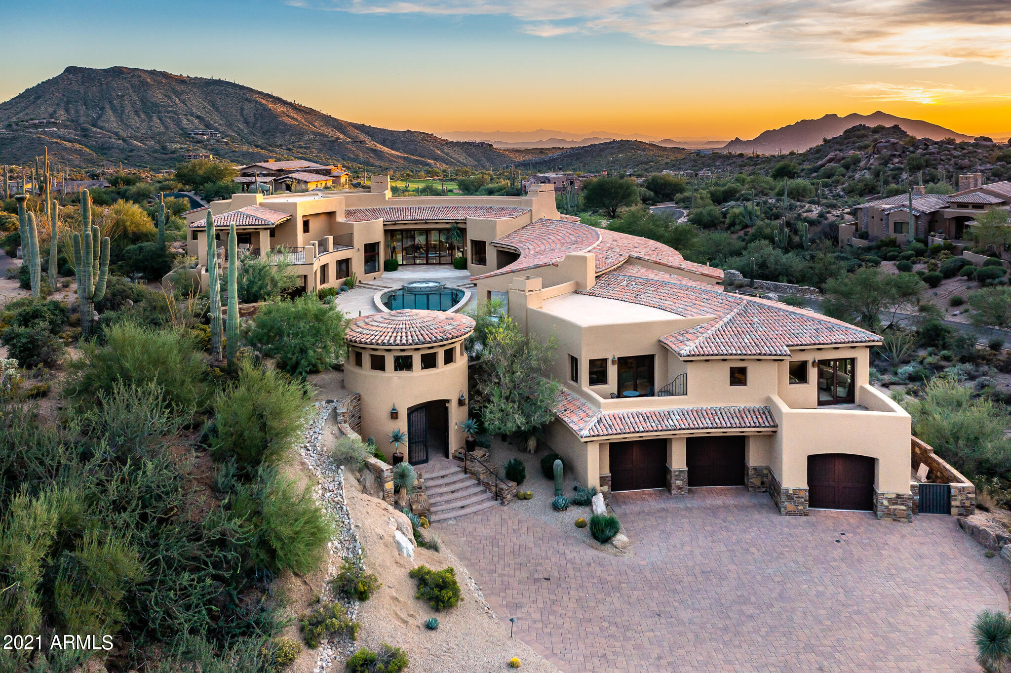 Saguaro Forest 261 is an architecturally significant 10,237 s.f., exceptionally private custom-designed home with, among other features described below and in supporting documents, five bedrooms and a luxurious library/office.  It is on a 1.54-acre homesite next to the fifteenth fairway of Chiricahua, one of Desert Mountain's seven courses, in semi-mountainous High Sonoran Desert terrain in far north Scottsdale.  It is an extraordinarily quiet and peaceful setting, far from any noisy roads.  Think ''resort escape'', or ''multiple family compound''! Taxes are low, too, at only $18,639 for 2021. The home is shaped like a horseshoe, open to the northeast, where the best views are, of nearby large granite boulders, beautiful desert vegetation, and the Continental Mountains about a mile and a half away, notably the landmark "Apache Peak".  This open end is also where, at a carefully designed "arrival point", visitors get their first, real "look" at the home after experiencing an impressive "arrival sequence" (described below).  The east side of the horseshoe is about half as long as the west side and has two levels.  The formal entrance to the home, a classy foyer, is on the lower level, and what is essentially an in-house, two-room casita with a covered outdoor patio/view deck with fireplace, is on the upper level above the foyer, accessible from the arrival point via an outside staircase.  (More on this "casita" later).  

The home was completed in 2013 after being bought in 2012 by an East Coast couple as an incomplete speculative home.  They completed it well, using materials and finishes far superior to what would have been in the home otherwise.  The large (2,800 square feet), limestone tile decked pool patio in the middle of the horseshoe is the home's centerpiece and features a completely re-built, 34' long, SICIS tile pool and spa (illuminated, with spillovers) in the shape of an arrowhead, designed by noted designer David Tisherman (whose work has been featured on the covers of Architectural Digest and the Robb Report).  This area is more of a "Pool and Party Plaza" than a mere "pool patio".  It is a remarkable space and serves as a dramatic internal visual focus point from the main public rooms. 

In addition to being the "star of the show", the Pool and Party Plaza is ultra-private. There is approximately an acre of open desert between the home and the nearest neighbor to the north, and there can be virtually no eye contact between someone at that home and someone in the Pool and Party Plaza due to the skillful placement of a tall, round, gated entry rotunda that serves as the home's "outside" front door.  Split-second glimpses of golf carts can be seen on a cart path to the east of the home, but due to vegetation and the way the east side of the home was designed golfers in these carts can only see a small part of the northern part of the Plaza.  And, taking that quick glance will put them at risk of driving off the path into some rough desert.  
 
In addition to the home's distinctive shape and the Pool and Party Plaza, other "architecturally significant" highlights include: a "transitional" mix of traditional building materials on the exterior of the home (natural stone, tile, and stucco) unexpectedly paired with a very light and bright, "contemporary" interior; beamed ceilings; rich-looking stone and wood interior finishes; many windows, adding to the interior's light and bright nature and making some awesome views very easy to enjoy; the home being artfully spread out over four main levels, creating wonderful interior sight lines and making for great views from the upper level windows (an elevator just inside the home on the garage level makes hauling groceries upstairs a breeze).   The home's expansive interior walls, daytime interior light levels, dedicated lighted art shelving, and art lighting, makes it perfect for the display of important art. 

The special "arrival sequence" starts with a visitor driving down a curving, descending, 57-yard-long, paver stone covered driveway, flanked by huge granite boulders, three Giant Saguaros, to a large auto courtyard, approximately 1,930 square feet in size.  To the right of this courtyard are three separate wooden garage doors, which provide access to a garage with room to park four cars due to one of the bays being roughly 40' long.  The home from this vantage point is two stories tall and makes an impressive first impression.  To the left of the auto courtyard is the rotunda, double-gated and remote controlled for security.  It is seven steps above the auto courtyard and makes for a very dramatic entry statement, with a tile roof and double iron gates.  

Walking up the steps to the rotunda, a visitor will start to notice the lovely physical textures of the home, a combination of painted stucco, rich-looking stone, traditional barrel vault tile, and landscaping, lots of landscaping! When they get inside the rotunda, with its brick flooring and custom light fixture, they will start to sense that they are entering an unusually beautiful home!  After passing through the rotunda, they will walk about seventy-five feet, climbing a few steps on the way, to reach the "arrival point", just a few steps below and to the left of the proper entrance into the Pool and Party Plaza and a place from which they can start to get a feel for the scope of the Plaza and the home.  This arrival point is graced by a long, low, stone clad planter filled with mature vegetation and an impressive piece of sculptural art.  From this vantage point, they will now realize the depth, breadth, texture, privacy, and overall scale of the Plaza, the home, and where the actual front door is, a few yards away to the left.  

Front Door and Foyer - It is a light-transmitting, wood and glass double-door affair that lets in maximum light.  The foyer has tall ceilings, an elegant travertine floor with marble insets, a big crystal chandelier, and curves around a gallery with tall windows that afford great views of the Pool and Party Plaza. It has a long wall perfectly suited for the hanging of large art.  

Casita   Instead of heading for the front door from the Arrival Point, a visitor can ascend stairs to the left which lead to a covered, upstairs balcony patio with a fireplace and seating area, essentially the "front porch" for an in-house, second story, two-room casita, with access from the other side of the casita down into the living room via some impressive stairs.  This patio has spectacular views of the golf course to the east, the mountains to the north, and the Pool and Party Plaza below and to the west.  The casita patio is pre-wired for media and would be one of about seven places around the home one would consider settling down with a cup of coffee or a glass of wine for a few moments.  The first room inside the casita from the patio is a combination living room, media room, game room with wet bar, and kitchenette.   It enjoys wonderful views through large picture windows due to its elevated vantage point.  Down a short hall is a powder room and a spacious, ensuite guest room.  On the other side of the hall is a cedar lined closet for out of season clothing storage.  This closet could be converted to a second elevator.  

Master Suite   This large bedroom is both a "retreat" from the rest of the world, and a "treat" for the eyes, with hardwood floors; a high, beamed ceiling, a private patio, and a honey onyx accented raised hearth fireplace.  The master bath is appropriately large, but proportionally so, and shows off a honey onyx accented lighted feature wall, laundry facilities, and a single large closet with gorgeous, dark-stained hardwood cabinetry, a large center island, and mirrored glass fronted cabinet doors, all of which combine to create a space truly deserving to be called a "Dressing Room".  

Kitchen    Beamed ceiling; a mostly Thermador lineup of appliances, including a six-burner gas range top with griddle; a large center island with seating for four; two wall ovens; two dishwashers,  and a warming drawer; has a Wolf microwave and Sub-Zero side-by-side refrigerator/freezer (Model 642); two sinks; large walk-in pantry (fitted out for a second refrigerator/freezer, a more convenient location than the garage); nearby is an undercounter refrigerator/icemaker, in granite slab-topped "pony wall" separating the kitchen from the family room; plenty of room for at least a six-top family dining table under a contemporary chandelier; immediate and easy access to the outdoor living room and the Pool and Party Plaza.

Family Room   Fully visible from the kitchen, thanks to a wide opening above a low, stone-topped storage cabinet.  Travertine tile floors; great views to the north through some windows and of the Pool and Party Plaza in the other direction; fireplace on a raised, marble-covered hearth, such hearth extends five or six feet to the north to provide a great visual "foundation" for the room.  

The various levels, intricate design details, and open interior architecture make for interesting internal sight lines, and all the windows, many on both sides of a room, help bring the beautiful outdoor setting and views "indoors".  Of course, these multiple levels require some steps and stairs between them, but they are beautifully constructed and finished and are exciting visual elements in and of themselves.  

For additional details on the home, please see the separate Summary of Architectural Highlights in the Documents section, and enjoy the collection of wonderful professional photography on the home.  For additional information on the Saguaro Forest and Desert Mountain, please see a document of that name in the Documents section. 

Regarding membership in the Desert Mountain Club, a wait list may apply for all Membership categories. A thirty-day Membership application review and approval is required.  Contact the Club prior to writing a property purchase contract.
