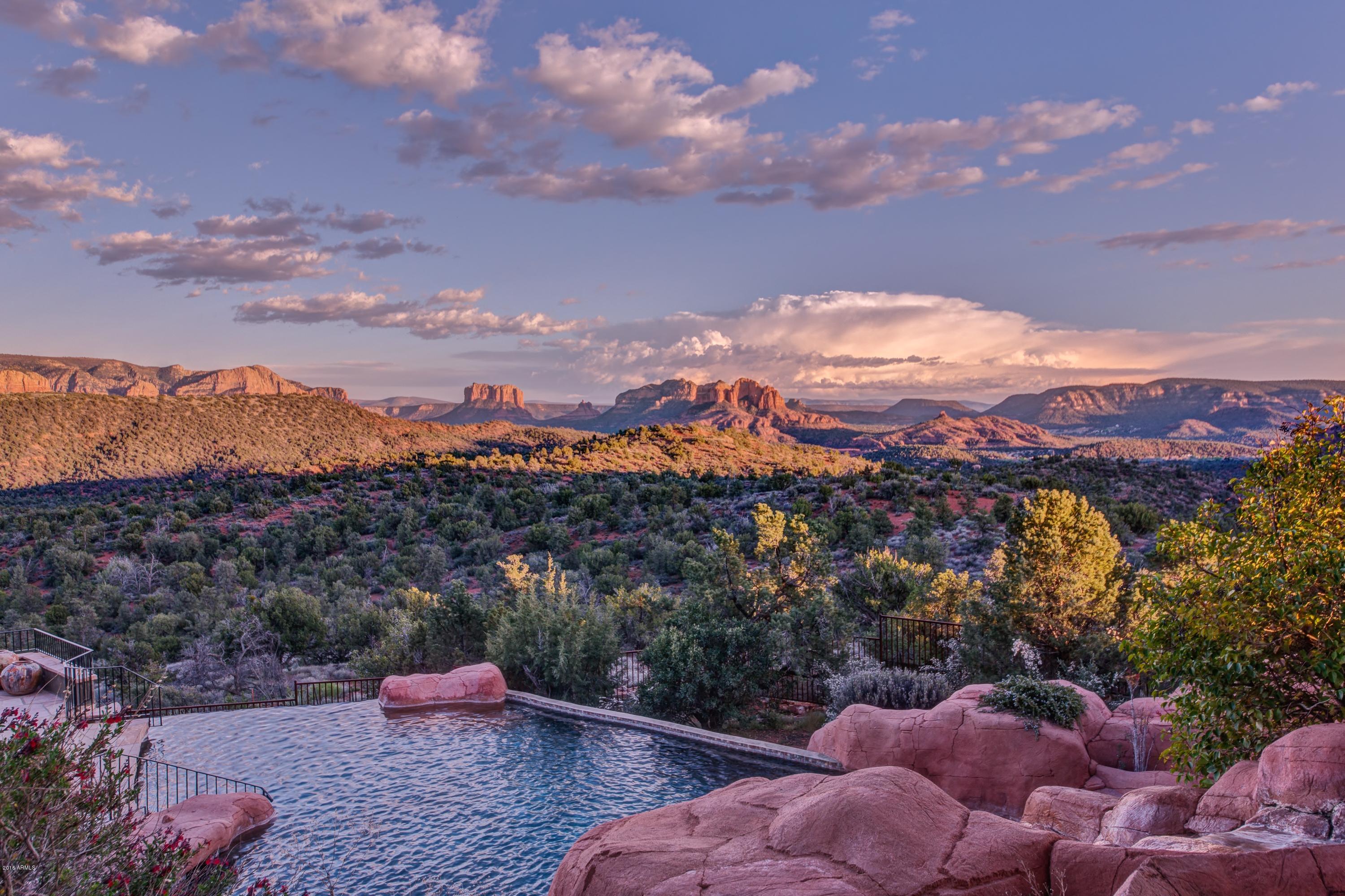 Thinking about a second home or full-time residence in Sedona and uncertain about this investment purchase?  Owner willing to lease (1year) with the option to purchase.  Owner willing to carry note with acceptable terms. Move-In Ready! Sedona's most incredible and luxurious red rock views with acres of National Forest in your back yard.  This one-of-a-kind Rustic Pueblo/Sante Fe masterpiece has everything: Gated Community, Hilltop location offering a semblance of privacy sought after by celebrities, incredible pool with grotto & spa, steam room for 8-12, exercise area in master bedroom, gourmet kitchen + wet bar, den, outdoor view decks + 2 outdoor fireplaces, private guest quarters upstairs, elevator, 3 car extended garage and more!  Transfixing beauty and unobstructed panoramic views! Spectacular gourmet chef's kitchen and appliances with entertainment bar.  Allow guests to enter the guest suites on the upper level with their own elevator and private entrance.  Master suite (main level) with exquisite views, patio and indoor/outdoor fireplaces.  Office/Den (or Fourth Bedroom) with Kiva custom fireplace, custom wood cabinetry, wood flooring, full bath with large walk-in steam shower and private deck seating.  

Guests will enjoy the magical and transfixing beauty with architectural inspiration from Native American Indian pueblos (petite nooks) crafted into an exterior red rock wall t(showcasing your favorite art collectible); red rock waterfall feature provides tranquil sounds while you sit under the masterfully rustic trellis where your favorite floral vines provide shade and shelter.  Evocative Navajo Indian  "Mother Earth, Father Sky" stained glass window painting depicts such a powerful image as the entirety of the universe, standing as a visual embodiment of our relationship to all that is.
          
MAIN LEVEL - LIVING ROOM | GREAT ROOM | FORMAL DINING | KITCHEN | BREAKFAST NOOK | BAR | POWDER ROOM | OUTDOOR PATIOS | ELEVATOR - Gorgeous wall to wall windows effortlessly disappear into the "pocket wall" while seamlessly enhancing your indoor-outdoor connection.   Perfect entertainment home with a bar grand fireplace, formal dining area; gourmet kitchen area with a chef's island and additional six inch granite island for guests; gorgeous cabinetry; art lighting throughout.  Complete "open floor concept" with an incredible entertainment flow.

MASTER BEDROOM AND BATH - As sunrise begins, with a hit of a button, shades rise and Sedona's spectacular colors bounce off the red rocks.  Enjoy your favorite refreshment just outside your master suite's private patio area with an exterior fireplace or relax inside with and enjoy tranquility in the evening with your Kiva fireplace.  A gym area off the master bath suite inspires you to enjoy a full 'spa-like' experience. Circular tile shower with marble bench and windows facing the four cardinal directions: north, south, east and west and a door leading to your private meditation or sunbathing corner.  Complete 'His and Hers' walk-in closets with custom built-in cabinetry.

OFFICE OR FOURTH BEDROOM WITH FULL BATH - Offering a spacious office suite with gorgeous custom wood cabinetry; full bathroom and large steam shower; private outdoor seating deck; spacious closet; Kiva fireplace; art lighting and surround sound.

THREE CAR GARAGE - Extended three car garage with room for your outdoor toys

UPPER LEVEL - TWO GUEST BEDROOMS | TWO BATHROOMS | LOUNGE | PRIVATE PATIO & ACCESS TO THE THIRD "VIEW DECK" - Guests may enjoy their own private entrance to the guest suites without entering the home.  Another elevator access inside located inside the home's foyer.  The second level features a second guest suite, full bath secret rotunda with a child size 'lookout port hole'.  A third guest suite, third bathroom with shower and guest lounge with bar and fireplace.  

   
ADDITIONAL AMENITIES
* Saltwater Pool (non chlorinated salt filtration)
* Appliances Viking Commercial Grade - (2) Beverage Refrigerators, 3 
  Dishwashers, Chest Freezer In Garage (Sears), Mobile BBQ Grill (Paid 
  $10K)
* Stacked Adobe (Energy "Green" Feature)
*  Wall Interior Are 3 Coat Venetian Plaster Over Adobe Walls
* Ceilings Are Exotic Rainforest Wood & Wood Beams Extending Outside 
  The Room 8 Feet
* Glass Is 10 Ft and Sliding in Living Room/Dining & Sliding Hidden 
  Pocket Glass Doors On Sides Facing North & South For Amazing 
  Indoor|Outdoor Entertaining Experience
* Stained & Finished Concrete Flooring 
* Furniture Available For Purchase Outside Escrow
* Pool & Grotto Cave With Heated Spa
* Bath House with Spa-Like Steam Room & Half Bath
* Security Cameras Located At Front Entrance and Pool Area
* Innovative and artistic rustic design fixtures
* Electric Shades
* Furniture Available For Purchase Outside Escrow
* Water Feature at Front Entrance
* Radiant Heated Concrete Flooring
* Steam Shower In Bathroom Located In Office/Den Or Fourth Bedroom 
  (Conversion)
* Natural Gas
* Bordering National Forest 
* Garage (3) Car With Auxiliary Storage Room
* Master Bedroom:  30' x 20' 
* Master Bedroom Closets: (2) 11' x 13' & 9' x 15'
* Guest Bedroom 1:  17' x 16' 
* Guest Bedroom 2:  14' x 24'
* Water Softener Is House-Wide (Entire Home) - Sodium Free System ($15-
  $20K Upgrade)
* Fruit Trees
* Six (6) Gas Fireplaces: Indoor Master Bedroom, Living Room, Den, 
  Upstairs Guest Lounge/Bar, Patio Outside Master Bedroom, Upper Deck
* Elevator (Accessibility AT Front Entrance For Private Entrance Or Inside 
  Foyer)
* Skylights With Ventilation
* Custom Draperies
* Commissioned Artist Stained Glass Window Navajo Indian "Mother Earth,   
  Father Sky" 
* Exterior And Interior Stone Work Imported From Colorado
* Smart Home Pro System
* Water Feature At Front Entrance
* Radiant Heated Concrete Flooring
* Steam Shower in Bathroom Located In Office/Den or Fourth Bedroom 
  (Conversion)
* Natural Gas
* Bordering National Forest 
* Panoramic Views 
* Venetian Plastered Walls
* Fruit Trees
* Six (6) Fireplaces: Indoor Master Bedroom, Living room, Den, Upstairs 
  Guest Lounge/Bar, Patio Outside Master Bedroom, Upper Deck
* Elevator (accessability near front entrance for private entrance or inside 
  foyer)
* Skylights with Venitilation
* Custom Draperies
* Commissioned Artist Stained Glass Window Navajo Indian "Mother 
   Earth|Father Sky" 
* Exterior and Interior Stone work imported from Colorado
* Smart Home Pro System
* Three Car Garage
* Fish Pond with pump On Entertainment Living Room/Dining Patio
* Trail access to national forest from property and hike to creek
* Sedona Airport - Private Aircraft OK (1 Mile long runway & 100 Ft Wide).