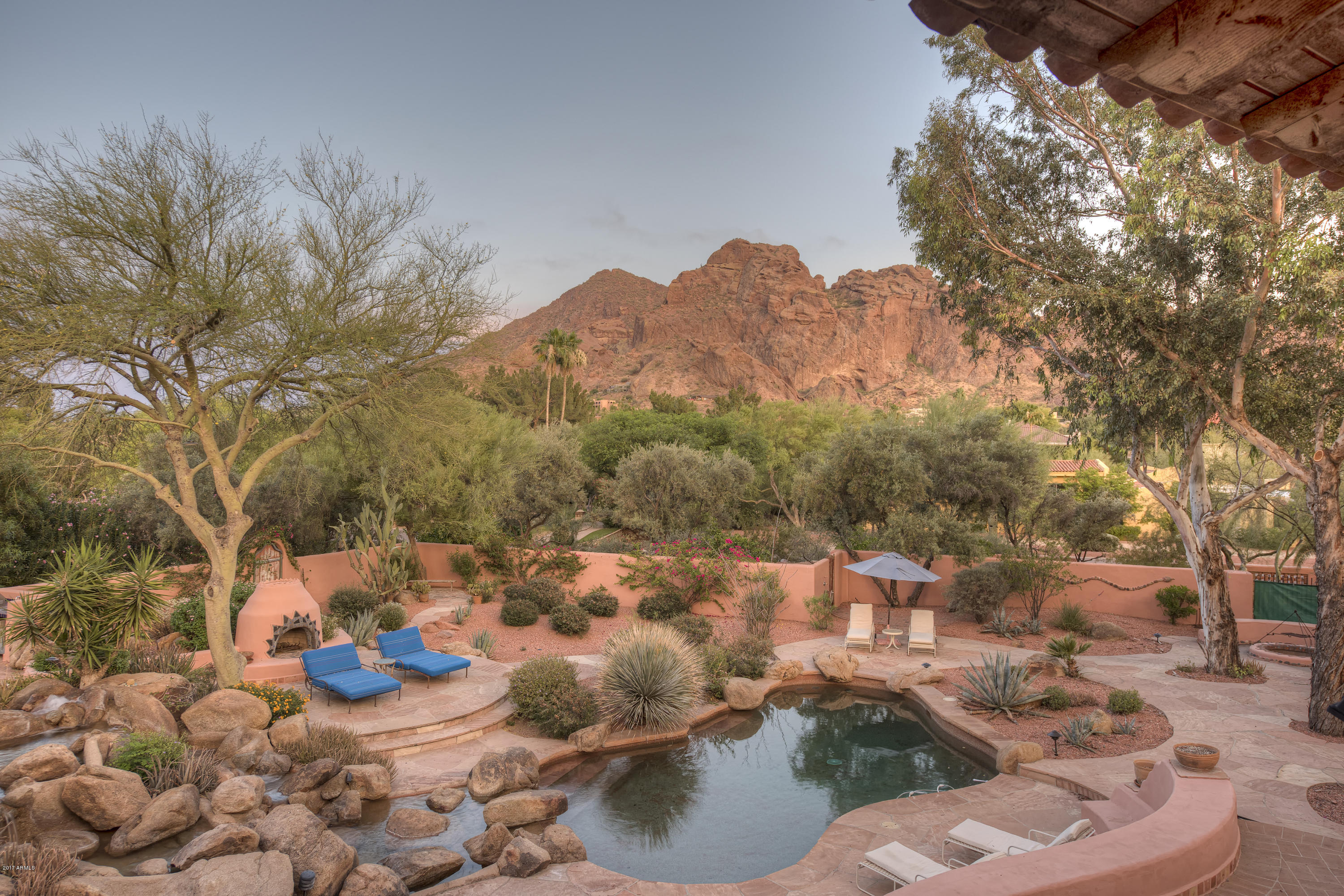 Arizona living at its finest. An artistically inspired estate with gated privacy and iconic Camelback Mountain views.  Showcasing botanical specimens and a variety of mature trees, the resort backyard, lush setting and huggable mountain views, make for an unparalleled Paradise Valley experience. Two master suites, two guest rooms, an office and separate enclaves make for relaxed living throughout the home. The artistic attention to detail is unsurpassed. Antique hand carved doors in both the interior and exterior, exemplary painted touches throughout and a flowing floor plan make this a truly signature home. The private approach & secondary entrance highlight the cobble stone circular driveway and water features. This unique home and its stellar setting form an entertainer's delight. Photography to be updated to reflect current changes in home.
