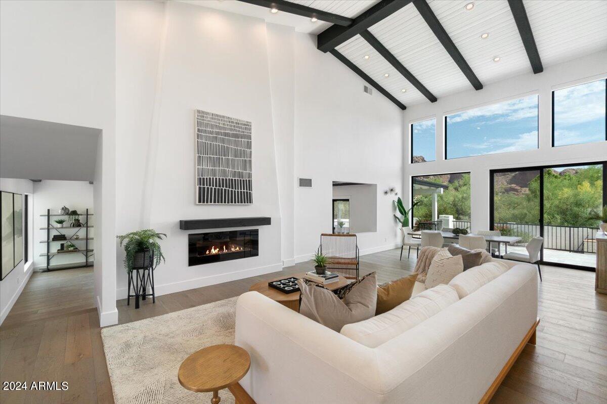 Love Paradise Valley but want an updated home? Remodeled down to the studs in 2019/2020, this home offers updated kitchen, baths, flooring, and even new plumbing.
Views of Camelback Mountain are visible the minute you enter, and from the entire rear of the property, inside and out. 
Warm wood floors welcome you into the home and a cozy bar is set in the corner of the living room with brass shelving supports, and both verage and dual zone wine coolers.  Beamed Ceilings give a nod to the history of this contemporary style home, allowing any style of décor to blend.
The first of three fireplaces graces the living room, which is open to the dining area.  A very spacious family room is just steps away with it's own fireplace. With an opening to the Living/Dining areas, this floorplan is wonderful for entertaining.
The Kitchen has a fresh feel with white cabinetry, Quartz countertops, with contrasting black and brass elements.  A central island, induction Bosch rangetop, Sub Zero Refrigerator and Ovens, Microwave drawer and walk in Pantry provide an abundance of storage and top of the line appliances for culinary adventures.
One of five bedrooms is just off the Living Room and would be a great space for an office. An adjacent bath with shower allows it be whatever works for you.
The powder room sports a sophisticated feel with black millwork accented walls, black and white marble Hexagon floor tile, and brass accents.  The powder room is also accessible from the rear open space of the property.
The Primary Suite is a dream.  Large enough to include a separate seating area, customized closets, and patio access, this room is secluded from the other bedrooms.  The Primary Bath is well designed with marble and porcelain tile accents, a large walk-in shower, separate vanities and a soaking tub and fireplace.  
The remaining three bedrooms are spacious, the largest with an en-suite bath. Another bath is shared by the last two bedrooms.
One of the family's favorite spots is the large media room.  There is more than enough space for this to be a playroom and study area, in addition to the media area. 
The laundry is large, with extra cabinetry and a drop zone just off the 2 car garage.
Outside, a raised patio keeps the views available, and overlooks the pool area.  A large low maintenance turf lawn leads to the sports court.  The batting cage in this area does not convey with the home.