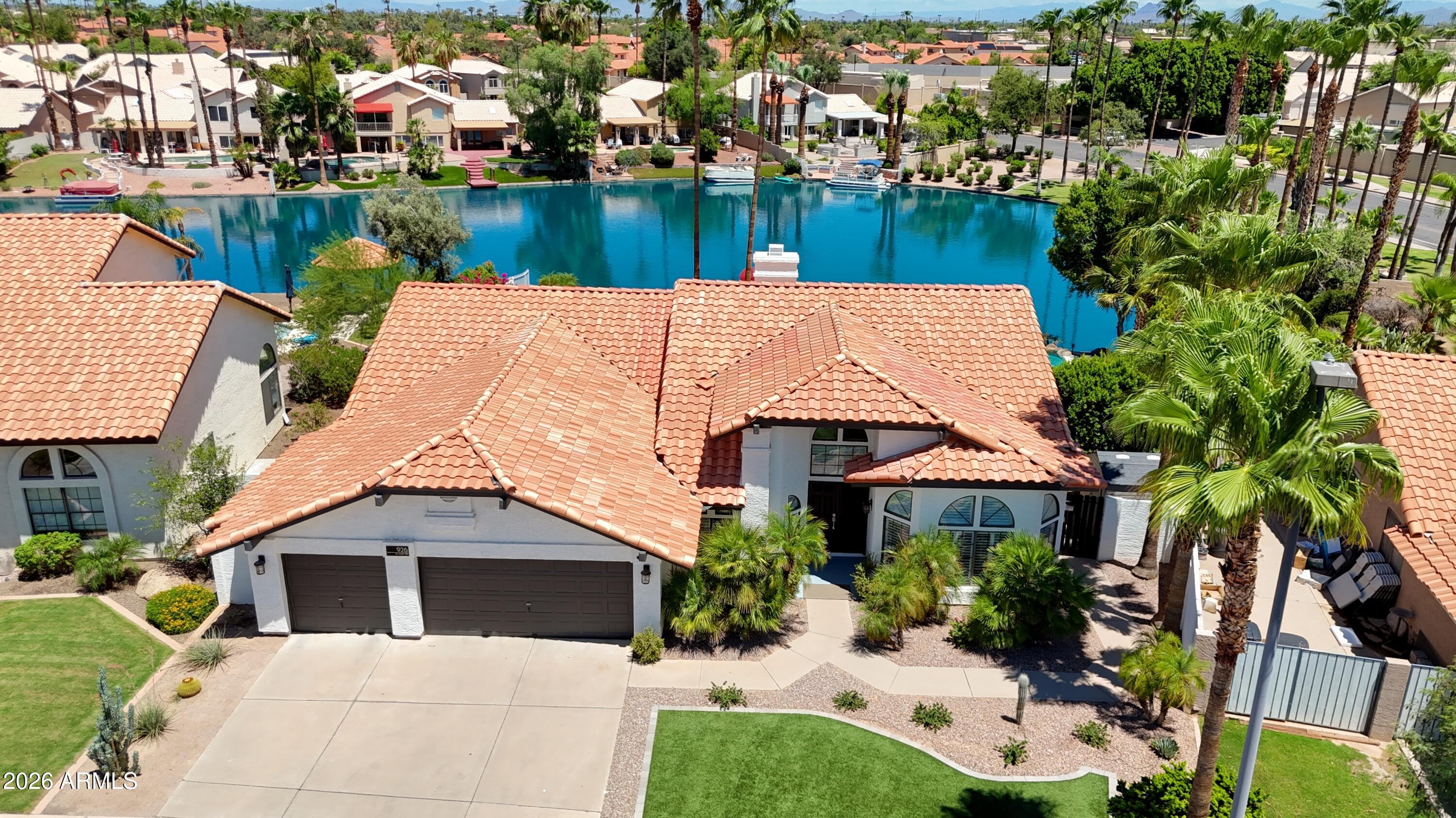 SINGLE LEVEL, UPDATED SINGLE-LEVEL LAKEFRONT HOME WITH A PRIVATE BOAT DOCK, RESORT-STYLE POOL & 3-CAR GARAGE! Every detail has been thoughtfully upgraded, including a new roof, new HVAC systems, refinished PebbleTec pool, new landscaping, exterior paint, and more. The chef's kitchen features custom cabinetry with pull-out organizers, NEW built-in Monogram refrigerator, NEW Bosch dishwasher, wine refrigerator, granite countertops, custom hood, travertine backsplash, and under-cabinet lighting. The luxurious primary suite offers French door to the lake and a spa-inspired bath with a frameless glass shower, multiple shower heads, and custom finishes. Additional highlights include vaulted ceilings, Pella doors, updated laundry room, new water softener, garage door openers, electronic blinds, and tinted windows, private workshop/storage, paver patio, artificial turf, beach-inspired side yard, and breathtaking lake views. Move in and enjoy the ultimate Arizona waterfront lifestyle!